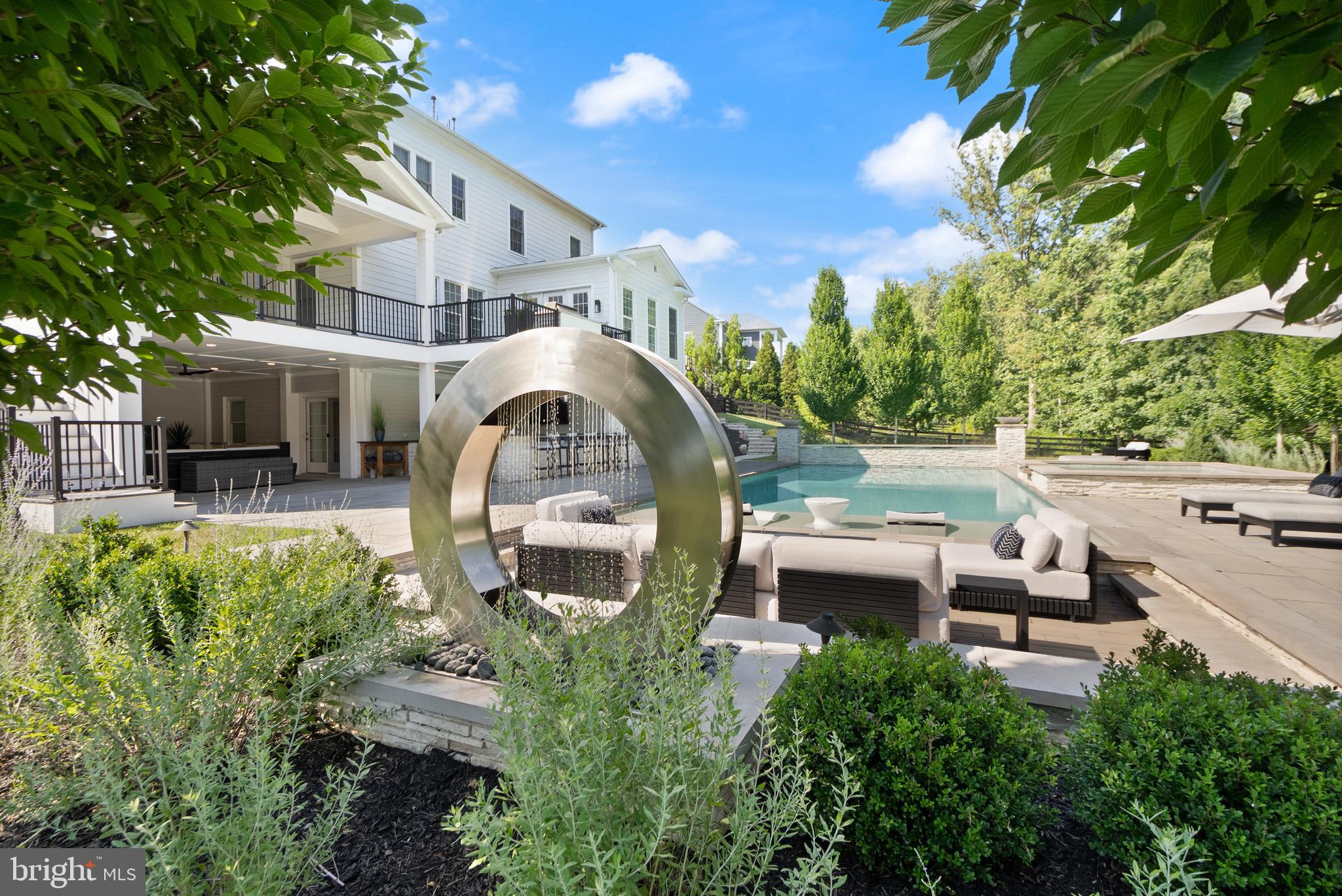 A breathtaking resort-caliber saltwater pool sets the tone for this extraordinary residence, delivering a true Ritz-Carlton–inspired experience in the comfort of your own backyard. Designed with a luxurious 7-foot depth and a premium soft-finish base, the pool invites both serene relaxation and elevated entertaining. A grand spa with cascading water feature and a striking designer ring fountain create a dramatic focal point, while evening uplighting transforms the entire setting into a private, five-star retreat.

Surrounding the pool, expansive custom hardscaping and a sleek track deck offer multiple spaces to lounge and gather—from elegant in-water loungers to a sunken conversation area centered around a modern fire feature. Dual fire bowls and a custom fire pit further enhance the ambiance, creating an atmosphere of warmth and sophistication reminiscent of the world’s finest resorts.

The outdoor living area continues seamlessly beneath the covered entertainment space, featuring a custom gas fireplace, a built-in natural gas grill, an outdoor refrigerator and ice maker, and all-weather TVs—perfectly designed for effortless hosting in every season. Thoughtful details, such as a Restoration Hardware umbrella and a premium outdoor fan, complete this refined outdoor environment.

Inside, the home carries forward the same elevated design with a brand new Luxury Vinyl floor, fresh designer paint, and upgraded lighting and fixtures throughout. A custom gas fireplace anchors the family room with modern elegance, while a desirable oversized main-level suite offers both flexibility and convenience for guests or multigenerational living. Custom craftsmanship is evident throughout, including coffered ceilings, a tray ceiling in the primary suite, detailed millwork, built-in office shelving, and a beautifully appointed butler’s pantry and mudroom.

Enhanced by a custom front entry, professionally designed landscaping, and a fully fenced yard, this home offers both striking curb appeal and peace of mind with updated major systems and appliances.

This is more than a home—it is a private retreat delivering a Ritz-Carlton lifestyle every day.

 This home sits in the award-winning Willowsford Community, surrounded by Loudoun’s wine country. Enjoy resort-style amenities—beach-entry pools, splash pad, lodge, fitness center, dog parks, sledding hill, tree house, and even a farm stand/CSA. Minutes from Brambleton and One Loudoun for dining, shopping, and entertainment, plus nearby Hanson Regional Park (257 acres!), farmers markets, Wegmans, wineries, and breweries. Convenient to Dulles Airport, Silver Line Metro, Tysons/DC, and top-rated Loudoun County schools.