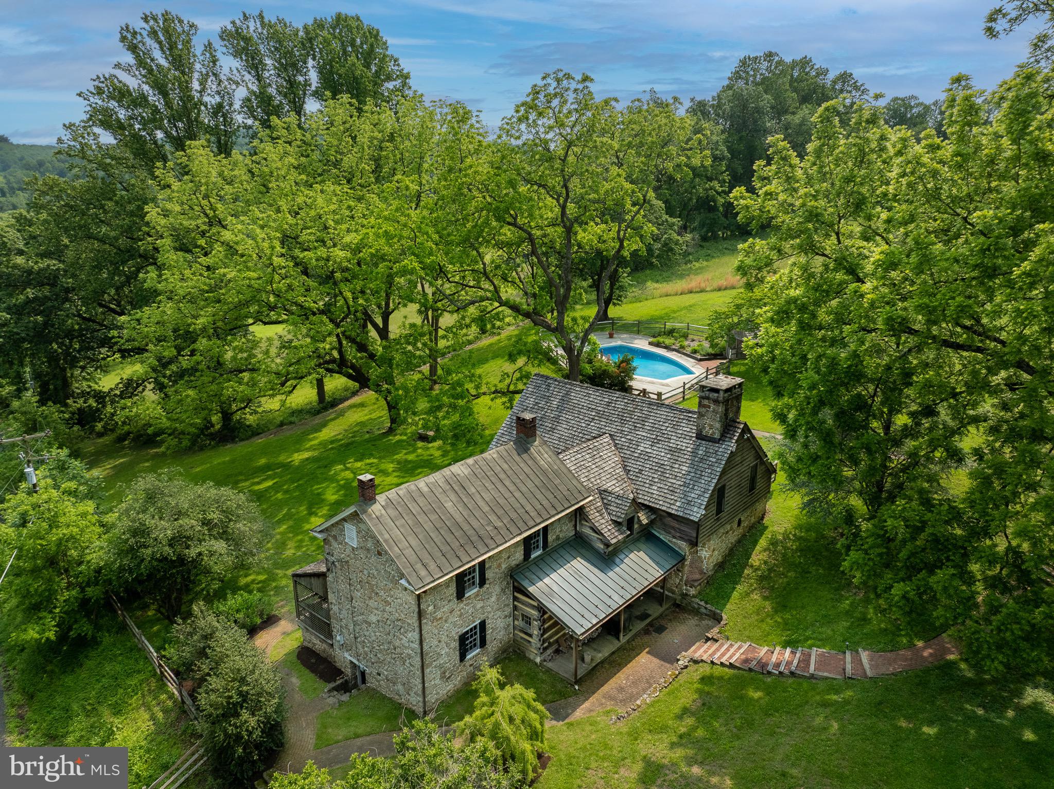 Welcome to 880 County Park Road. This 10+ acre property hosts one of the most unique and spectacular views in the Warwick Furnace Valley. It is situated near the top of County Park Road with expansive views from the entire property. The house contains 4 bedrooms and 3 full bathrooms (1/2 bath in Garage/Barn) as well as a great room, living room and dining room with exposed beams and hardwood floors throughout. The great room also contains a large stone walk-in fireplace and a beehive oven! Another unique aspect of the home is the metal bridge that connects the circa 1751  house to the addition (1910 and 1980). You might also enjoy the hot tub off of the primary bedroom, the large pool and pool deck with AMAZING views of the surrounding land, a dis-used tennis court that can host pickleball and basketball and lastly a detached barn with many possibilities! The newer barn has a first floor 2 car garage and second floor multipurpose room. The entire building is heated, insulated and has a 1/2 bathroom on the second floor! Leave it as a barn or reinvent this space as an office, garage, extra storage, yoga studio, art studio or much much more.  The entire property along with many surrounding properties are conserved with Natural Lands Trust to protect their natural beauty and purpose. Do not miss this opportunity to acquire one of Chester County’s most beautiful homes!
