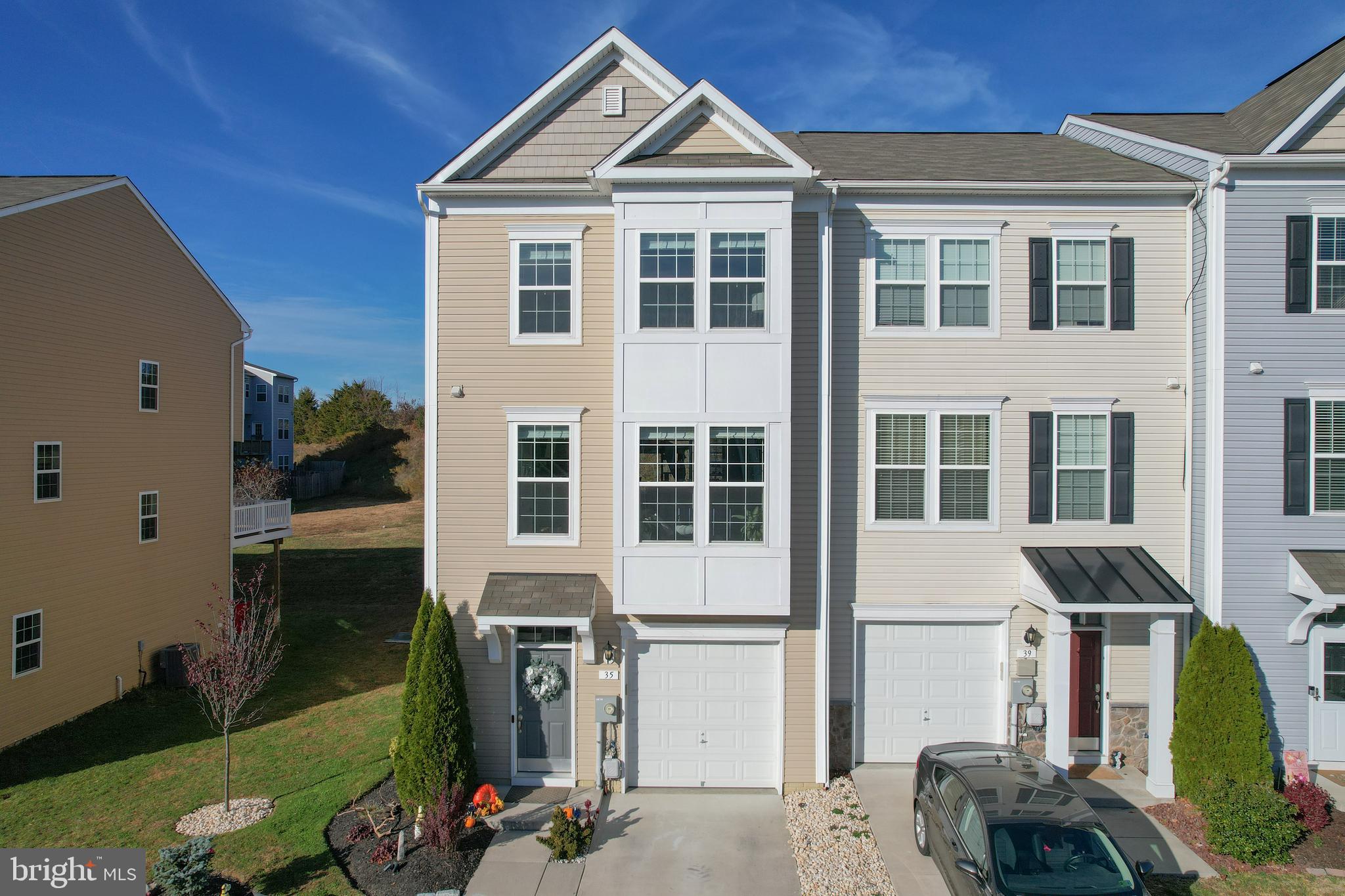 This spectacular end-unit townhome and former community model home offers elevated design, intentional detail, and a layout that quite literally stands above the rest. Featuring a full morning room extension on all three levels, this residence is the largest model in the community, creating rare additional square footage, enhanced natural light, and extra living space that you feel the moment you walk in.

Designed by a homeowner whose life revolves around precision and polish, the interior carries a soft, elegant shimmer throughout. The walls have a subtle sparkle finish that catches the sunlight as it shifts throughout the day, giving the home a luminous, inviting glow.

The main level is expansive, bright, and beautifully finished with glossy marble-style tile flooring. The living area stands on its own with dramatic natural light, luminous walls, and a nearby convenient powder room — perfect for entertaining and everyday ease. The added morning room extension expands the space even further, offering flexibility for additional dining or lounging.

The true showstopper is the oversized eat-in kitchen island bar, designed for real life gathering and hosting. From morning coffee to evening wine and conversation, this space is made to bring people together. The kitchen features dark granite countertops, painted cabinetry, subway tile backsplash, stainless steel appliances, modern pendant lighting, and an open flow ideal for entertaining.

Upstairs, the primary suite feels like a private retreat, complete with tray ceiling, seating space and a sophisticated accent wall. A large walk in closet and modern soaking tub give function and luxury equal footing. The ensuite bathroom features dual vanities and spa-inspired finishes.
Two additional bedrooms with large closets and generous layouts share a full tub/ shower hall bath.

The fully finished walk-out lower level offers endless flexibility — perfect for a home office, guest suite, gym, or additional living area. A full bathroom and walk-out access to the backyard complete this level.

Outside, the home continues to impress with a double-tiered deck and patio system showcasing extensive hardscaping, raised planter beds, integrated outdoor lighting, and designer string lighting for evening ambiance. The covered upper deck is ideal for entertaining, while the lower patio with built-in seating creates a cozy destination for relaxing nights and small gatherings.

A one-car garage, driveway parking, and a highly desirable Falling Waters location near I-81, I-70, shopping, restaurants, and commuter routes complete the offering.

As the original model home and largest in the community, this property offers something truly special: space, light, polish, and presence — all in one exceptional package.  Set up your private tour today and see for yourself!