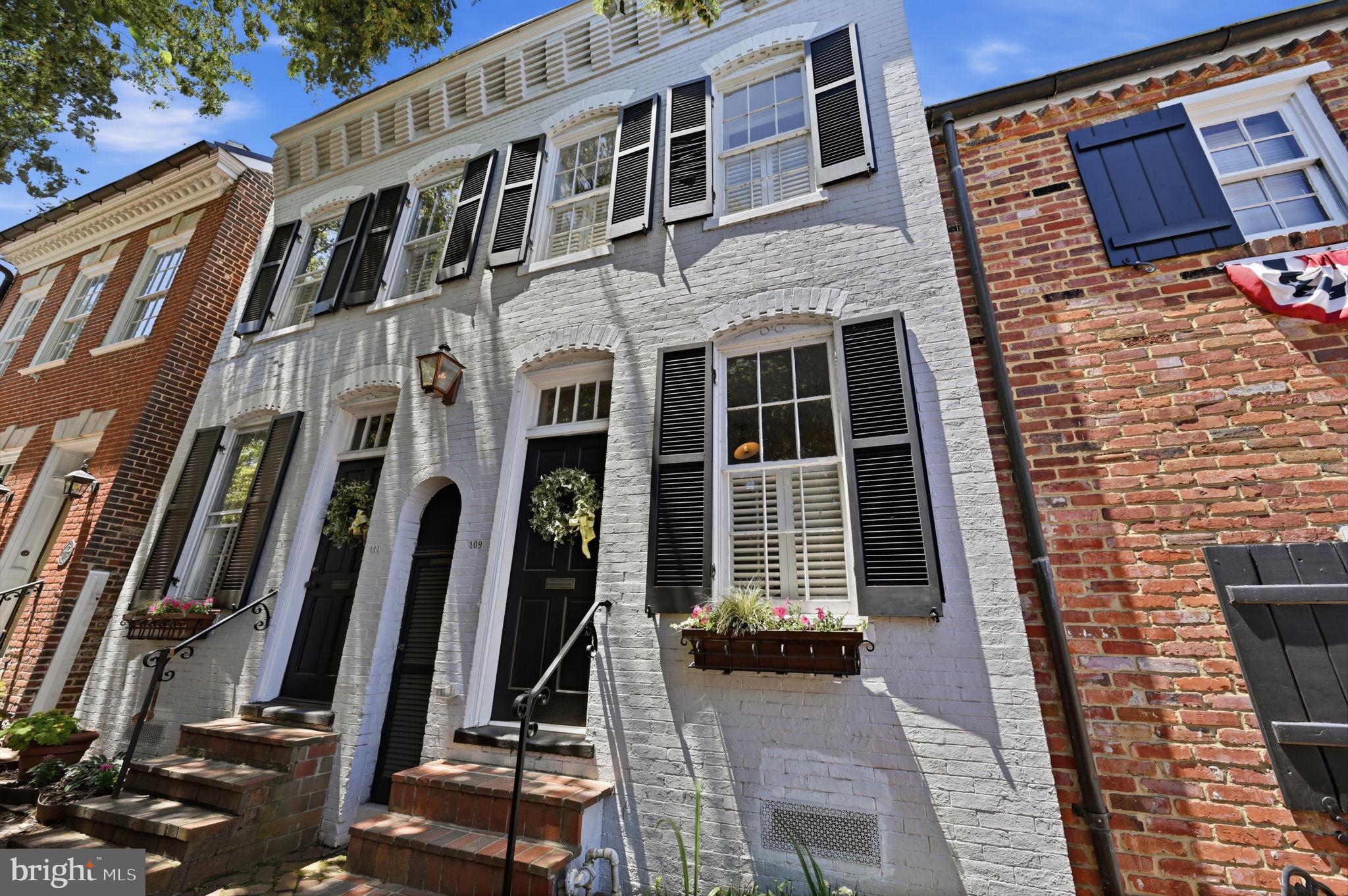 Rarely available in Old Town's coveted southeast quadrant, this exceptional 25-ft-wide semi-detached brick home spans 2,084 square feet and was born from the thoughtful union of two separate residences circa 1880. Enter through either of two front doors into a home of genuine character: a local artist's interior mural depicting the Lee Street streetscape, 9-ft ceilings, original hardwood floors, and two gas fireplaces set the tone throughout.

Two distinct living areas, a spacious dining room, and a comfortable family room flow toward a stunning chef's kitchen with expanded marble countertops and top-of-the-line appliances. French doors open to a private, professionally landscaped stone-terraced courtyard and garden complete with a wood-burning fireplace an entertainer's dream.

Upstairs, a fabulous primary suite features a luxurious soaking tub and a wood-paneled king-bed inset. Two sun-drenched front bedrooms, one with built-ins, and a full bath complete the level. Crown moldings, chair rail, wainscoting, recessed lighting, and two half baths add refined detail throughout. The home offers 3 bedrooms, 2 full and 2 half bathrooms, two gas fireplaces, and a wood-burning fireplace on the beautifully terraced and landscaped backyard patio. Steps to King Street dining, boutiques, and the free trolley; one block to the Potomac and Waterfront Park; minutes to Metro, Reagan National, D.C., the Pentagon, and the GW Parkway trail system. Old Town living at its absolute finest.