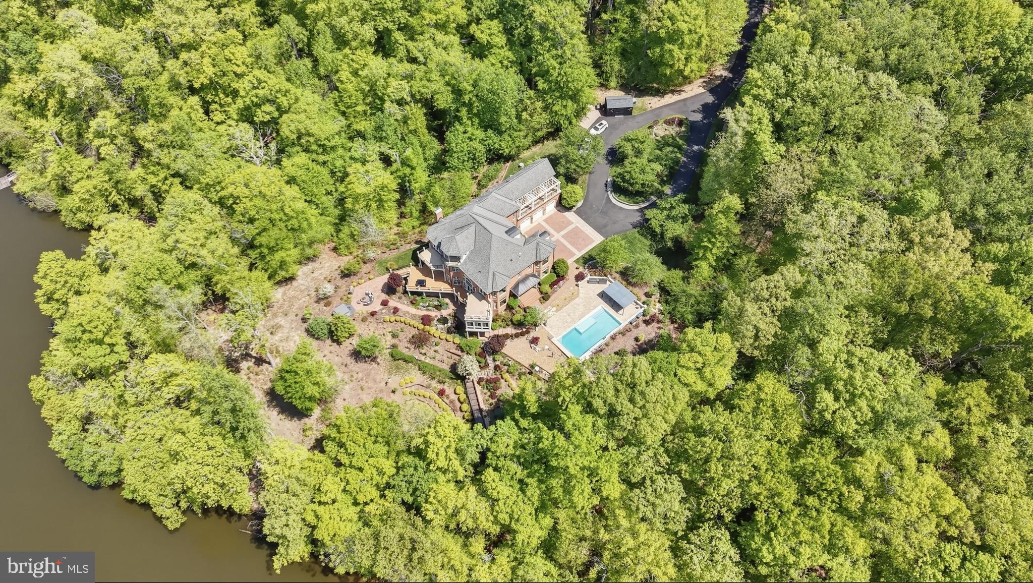 An extraordinary waterfront home set on five private, wooded acres with an impressive 392 feet of shoreline. This custom all-brick Renaissance estate spans nearly 9,000 square feet, offering sweeping water views from all four levels and timeless architecture, refined interiors, and a resort-style outdoor living space.

From the moment you arrive, the setting feels like a secluded retreat. Mature trees frame the home, creating a sense of privacy and tranquility rarely found with this level of waterfront access. Expansive outdoor living spaces—including seven balconies and porches—invite you to take in the water from every vantage point, while the sunroom, Trex deck, and stone patio create effortless transitions between indoor and outdoor living.

At this breathtaking waterfront resort, you’ll find an in-ground pool and separate hot tub that overlook the lake, while a private dock provides a permanent parking space with direct access for boating, fishing, and peaceful evenings on the water. The lake becomes a natural extension of daily life—perfect for morning coffee at sunrise, afternoon adventures, and unforgettable sunsets reflected across the water.

Inside, the home was thoughtfully designed to balance grand-scale entertaining with comfortable everyday living. A glass-walled elevator offers convenient access to multiple levels, adding both function and architectural interest. The residence features six en-suite bedrooms, each with its own private balcony—an exceptional design detail that ensures every bedroom feels like a private oasis overlooking the water.

The recently updated gourmet kitchen is as beautiful as it is functional. Outfitted with Café appliances, double dishwashers, a beverage refrigerator, and an expansive butler’s pantry with wine storage, the space is designed to accommodate gatherings of any size. Whether hosting intimate dinners or large celebrations, the flow between the kitchen, sunroom, garden room, and surrounding outdoor spaces makes entertaining seamless and memorable.

Upstairs and throughout the home, water views create a constant connection to the landscape. Natural light pours through well-placed windows, enhancing the home’s architectural lines and highlighting the peaceful setting beyond. Additional luxury investments include extensive landscaping and hardscaping throughout the grounds, along with a serene in-ground koi pond.

The walk-out lower level features nearly 2,200 square feet of fully-finished living area. The lower level offers a private bedroom with a full ensuite bathroom ideal for guests, extended stays or as an in-law suite. Entertainment is a breeze on this level thanks to the large recreation room, additional kitchen, powder room and theatre room. With direct access to the grounds and pool area, it functions beautifully as its own retreat within the home.

This is a rare opportunity to own a truly private waterfront estate where refined living, natural beauty, and thoughtful design come together in perfect harmony.