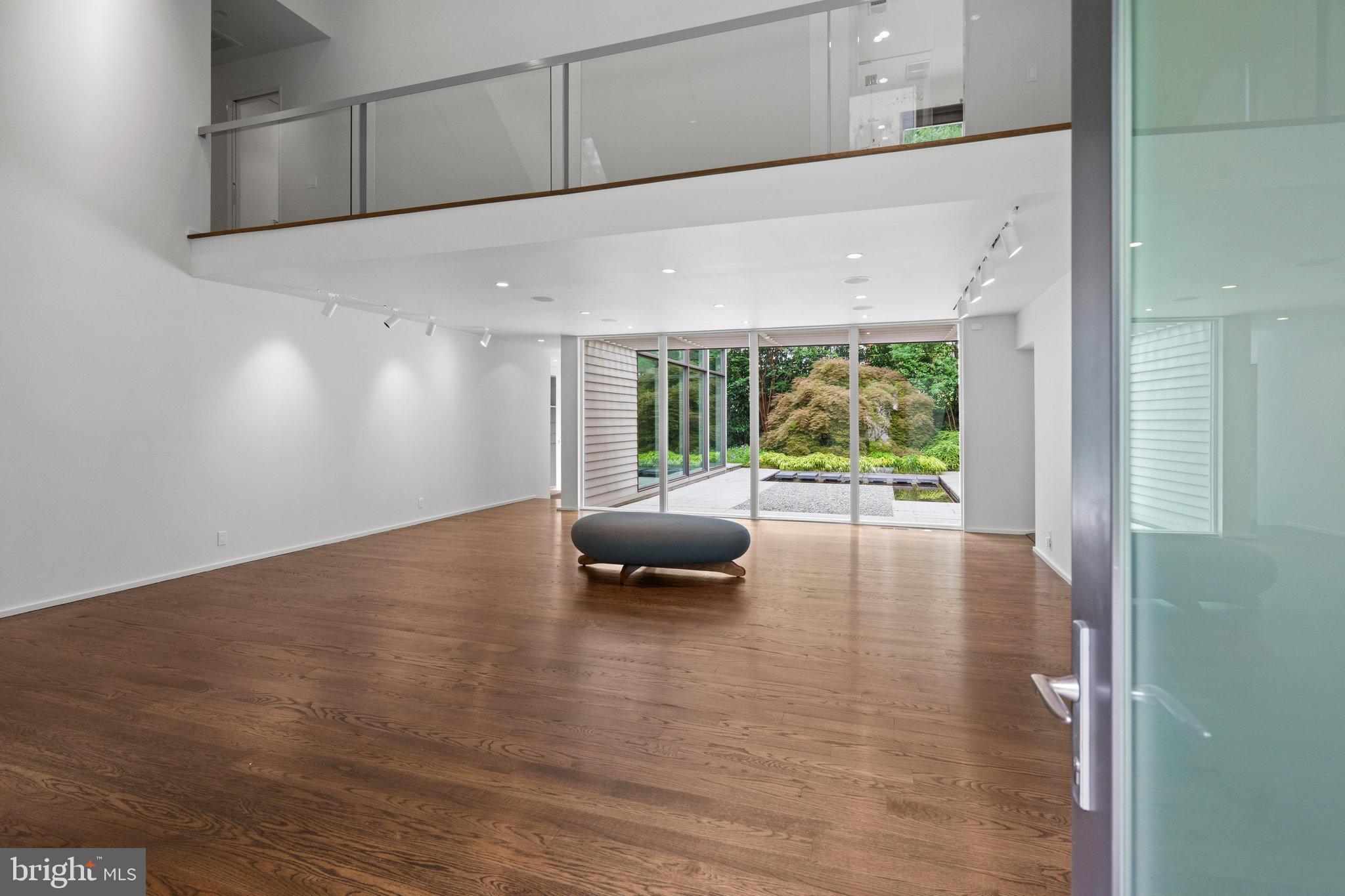 A spectacular modern take on a Chevy Chase Village classic Cape Cod, 5515 Center Street pairs architectural drama with remarkable ease of living. Sited on a large, manicured lot, the home is distinguished by its light-filled contemporary design, dramatic floor-to-ceiling windows, and exceptional details throughout.

The home's on-grade entry, elevator, open floor plan, and main-level bedroom suite provide remarkable flexibility now and for years to come. At 3,850 square feet, this is a rare opportunity to purchase a just-right-size home without compromise.

Curb-appeal abounds, but more impressive is the flagstone entryway that opens to a dramatic central living space with soaring 20-foot ceilings and a wall of oversized windows framing views of the lush grounds. Its generous proportions provide ample space for both living and dining, allowing the room to adapt easily for entertaining and everyday life. Designed to showcase art and capture natural light, the home shines with gleaming hardwood floors, modern recessed lighting, and curated fixtures.

Just off the living room, an adjacent family area offers a more intimate space for everyday living, along with convenient access to the elevator and a powder room, while a private sunroom offers another place for respite.

The first floor also includes a large bedroom (currently configured as a library). With an en suite full bath and walk-in closet, it provides exceptional flexibility for guests, an office, or a dedicated main-floor suite.

At the heart of the home, the sleek, state-of-the-art kitchen is a chef's dream, featuring a center island with breakfast bar seating, two dishwashers, double ovens, custom glass shelving, and rows of gleaming windows that bring a remarkable sense of nature into the home. With oversized table space, seating and tv space, and access to the garden, guests will easily float indoors and out, enjoying the sound of clinking glassware and cascading water in the gardens beyond.

Upstairs, the primary suite is a true retreat, with high ceilings, mature treetop views, an enormous walk-in closet, and a sumptuous en suite bath featuring a soaking tub and separate shower. From the gallery connecting the bedroom level and overlooking the great room below are two additional bedrooms, a separate storage room, and a renovated hall bath. Not to mention a washer / dryer for the ultimate convenience.

Two additional bedrooms, separate storage room, and a renovated hall bath radiate from the dramatic upper gallery that overlooks the living room, keeping the bedroom level connected to the heart of the home.

The lower level is primed for further finishing, with the main laundry area, utility, storage, and LVP flooring making it an easy future finished space.

5515 Center Street delivers something increasingly rare: privacy, architectural distinction, flexible living, and the tranquility of an expansive setting, coupled with the peerless amenities of Chevy Chase Village.

Chevy Chase Village is a historic community of 720 homes that was built as the original “streetcar suburb” to the Nation’s Capital. From its central location, residents are just steps to Friendship Heights, Metro, neighborhood shops and restaurants, and nearby Western Grove Urban Park, while still enjoying the tree-lined streets, brick sidewalks, mature landscaping, and unmistakable sense of place that define Chevy Chase Village. The Village Hall, community events, and exceptional municipal services add to the feeling of living in a close-knit neighborhood with conveniences just beyond the front door.