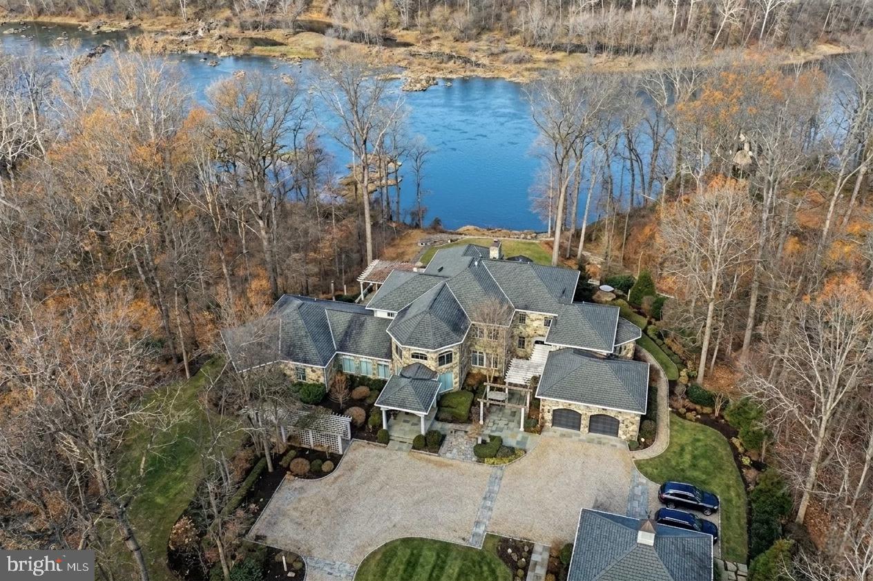 Breathtaking river views with access for fishing and kayaking.  Commanding an incomparable vantage point above the Potomac River, this extraordinary stone estate by BOWA defines timeless sophistication and total privacy on more than three gated acres in McLean’s most coveted enclave, moments from Washington, D.C.

Beyond its stately approach and manicured grounds, the residence reveals  16,000 square feet of refined interiors designed for both grand entertaining and serene daily living. A two-story great room with floor-to-ceiling windows frames sweeping river views, while French doors open to an expansive terrace that captures the tranquil beauty of the surroundings.

The gourmet kitchen is a showpiece with professional-grade appliances, granite surfaces, a walk-in pantry with Sub-Zero refrigerator, and a hidden bar. The main level also offers dual offices, two powder rooms, elevator access, and a full laundry with pet bath—all under soaring ceilings that enhance light and volume.

The main-level owner’s suite is a private sanctuary with windows on three sides, dual dressing rooms, and a marble spa bath with jetted tub, steam shower, and private balcony overlooking the river. Upstairs, three guest suites each feature walk-in closets and elegant baths, two with French doors to balconies.

The lower level is a destination in itself—featuring a lounge with stone fireplace, billiards area, wet bar, wine cellar, fitness room, and a stunning indoor pool with skylights and glass doors opening to extensive stone patios. Additional amenities include a private in-law or staff suite with full kitchen, a salon, guest suite, and generous storage.

Outside, terraced gardens, pergolas, water features, and a gazebo with full outdoor kitchen create a breathtaking resort-style setting. With five-car garage parking, geothermal systems, and whole-house generator, this distinguished estate offers rare scale, craftsmanship, and uninterrupted Potomac River views.