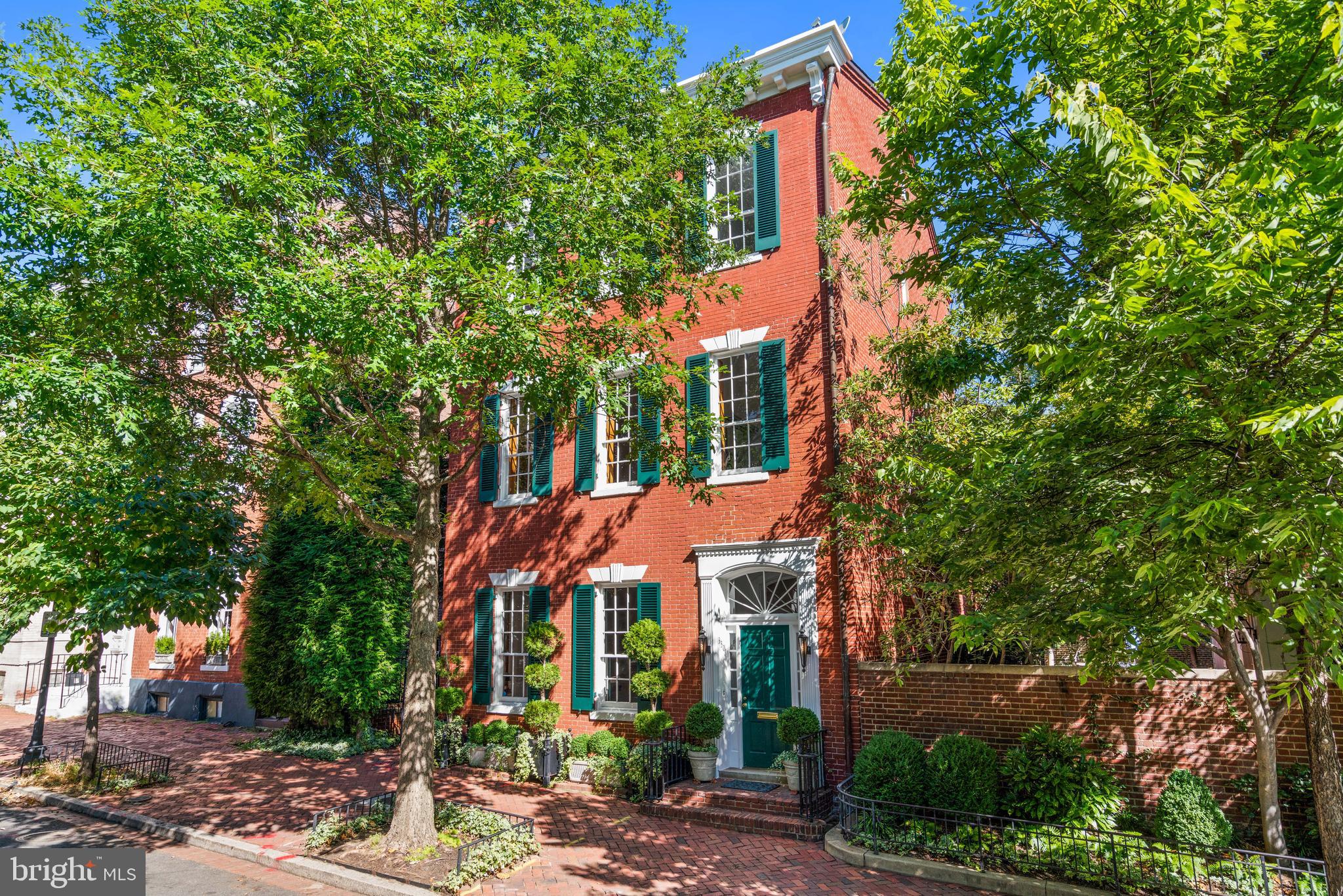The Marbury House, built circa 1811, 3307 N Street NW, Washington, D.C. is one of Georgetown’s most notable houses.  Its pedigree bridges the early Republic and the Kennedy Camelot era. Commissioned by William Marbury who was a prominent Georgetown financier, staunch Federalist, and the namesake of the landmark Supreme Court case Marbury v. Madison, the residence embodies the style and grace of Federal architecture while carrying an exceptional historical lineage. 
The façade is classic and timeless with rose-red brick laid in balanced courses and symmetrically aligned sash windows with deep green shutters.  There is a centered entry crowned by a delicate fanlight and a refined cornice that completes the composition. Eschewing ostentation, the design favors proportion, light, and restraint which are all hallmarks of the Federal style that make the home as elegant today as it was two centuries ago. The interior floor plan welcomes one with a gracious stair hall, high ceilings, and double parlor with large scaled spaces conceived for conversation, music, and entertaining. Further is the elegant dining with access to the generous and lovely gardens. The upper floors proved five bedrooms, numerous full baths, a library and an easily accessible walk up attic with high ceilings and windows.  The lower floor is well suited for staff with a private entrance.  Additionally, the property is enhanced by a one-car garage and two surface parking spaces. 
William Marbury’s ownership anchors the home in the nation’s formative years. A trusted figure in John Adams’ Federalist circle, Marbury served in key financial and civic roles in the capital’s infancy. His legal battle in Marbury v. Madison (1803) established the doctrine of judicial review, making his name synonymous with the balance of powers.  Thus, a distinction few American residences can claim. In this house, politics, finance, and the social life of early Washington intertwined, giving the property a provenance as substantive as its architecture. 
More than a century later, the house welcomed another chapter of American history when Senator John F. Kennedy and Jacqueline Bouvier Kennedy made it their Washington residence. Purchased in late 1957, 3307 N Street was the couple’s first owned home in the city.  It was a setting for young family life and rising national political ambitions. Their daughter Caroline and, in 1960, John F. Kennedy Jr. were born during this period. Jacqueline who possessed a discerning aesthete, reimagined the interiors several times by shaping the double living room into a warm, polished salon where she hosted “political teas” and small gatherings that subtly advanced her husband’s presidential prospects. 
During the 1960 campaign and transition, the townhouse became an informal nerve center. Advisors came and went through the gracious doorway; decisions about Cabinet appointees were considered in the front rooms; and, on winter mornings, the President-elect stepped onto the porch to share announcements with the press gathered along the brick sidewalks. On January 20, 1961, John and Jacqueline Kennedy departed this door for inaugural ceremonies. An indelible moment that fixed the house in the nation’s visual memory. Soon after, the property returned to private stewardship and it’s essential character preserved. 
Today, the William Marbury House offers what sophisticated buyers prize most: architectural integrity, enduring materials, large gardens spaces, ample parking and a storied address at the core of Georgetown’s village life. It is a home that has hosted statesmen and young families alike, where measured elegance frames modern living and where every arrival walks through a doorway shared by figures who shaped American history.