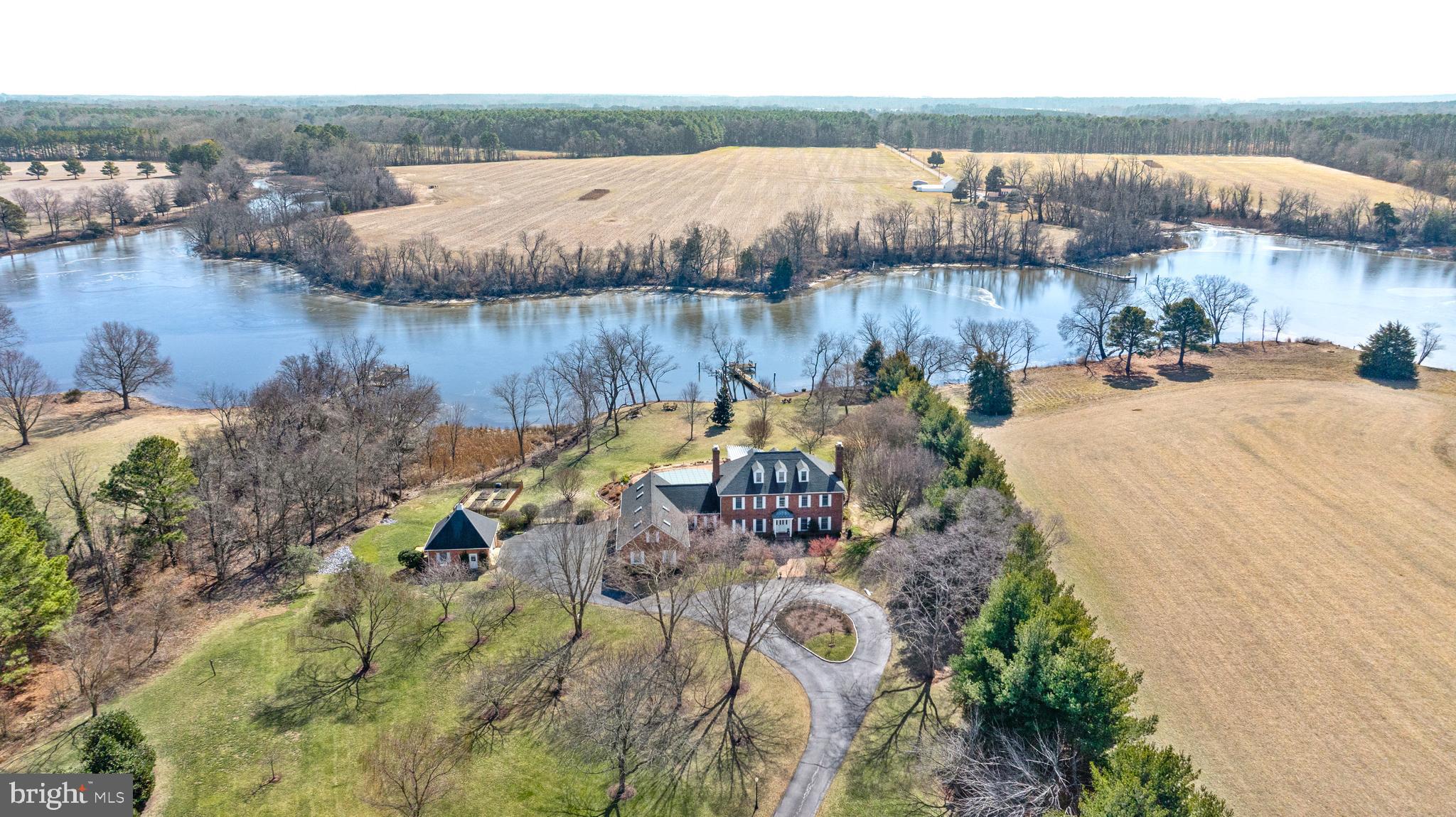 Nestled on 6± acres along the serene Island Creek in Patrick’s Plains, this stately brick manor offers an
unparalleled blend of timeless elegance and modern luxury. With three floors of beautifully designed living space, this sun-drenched home features breathtaking water views, exceptional outdoor amenities, and high-end finishes throughout. The main level boasts a primary suite, a formal dining room with a fireplace, and a sunroom filled with natural light. The room opens to an expansive deck, perfect for enjoying the waterfront setting. The gourmet kitchen is a chef’s dream, complete with a large island, professional gas range, SubZero refrigerator, and wine fridge. Upstairs, a second potential primary suite offers flexibility, with a private balcony providing a peaceful retreat. The third floor is an entertainer’s paradise, featuring a wet bar and powder room, perfect as a recreation space. Outside, the home’s resort-style amenities include an in-ground pool with an expansive deck, a large pergola, fire pit, and extensive hardscaping, all designed for seamless indoor-outdoor living. A private pier on Island Creek invites endless waterfront enjoyment. Car enthusiasts and hobbyists will appreciate the attached three-car garage and detached garage, along with a suite above the garage, ideal for guests or creative pursuits. With gorgeous renovated bathrooms, hardwood flooring throughout, and an abundance of natural light, this exceptional waterfront retreat offers a lifestyle of luxury, comfort, and tranquility.