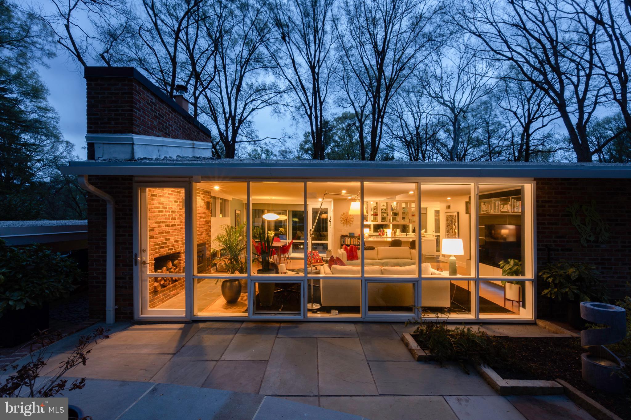 This stunning Mid-Century Modern home, located in the sought-after Hollin Hills neighborhood, was designed by renowned architect Charles Goodman. Offering one-level living at its finest, the home features three spacious bedrooms and two full bathrooms, with floor-to-ceiling windows throughout that bring in abundant natural light. The open living room is highlighted by skylights, recessed lighting, and a full wall of brick with a wood-burning insert fireplace, creating a warm and inviting atmosphere. A wall of built-in shelves neatly houses the TV, adding dramatic focal point.

The open kitchen boasts a breakfast bar, granite countertops, stainless steel appliances, and a wine fridge, perfect for entertaining. A large utility and pantry area is conveniently located off the kitchen, along with a washer and dryer area that includes cabinetry for additional storage. The completely remodeled hall bathroom features a unique skylight across the entire ceiling, creating a bright and airy space.

The primary suite includes an en-suite remodeled bathroom and remote-controlled custom shades for added comfort and privacy. The second large bedroom, currently being used as the primary suite, offers two closets and custom remote-controlled shades.  Flor brand carpet tiles in two of the bedrooms, chosen specifically from the Hollin Hills series.  Third light-filled bedroom is currently home office.  Custom closets throughout. 

A charming dining room area is enhanced by a Nelson bubble lamp, creating a stylish and inviting space for meals. Custom window coverings are installed throughout, ensuring a cohesive and refined aesthetic. Outside, the home offers extensive hardscaping and landscaping, featuring various patios and mature plantings designed with privacy in mind. A new sauna with a heater is an added luxury.

For practical amenities, the home features a rare oversized carport with an electronic car charging station and additional storage shed.
Hollin Hills offers membership to 2 community pools as well as membership to a tennis and pickleball club. The scenic neighborhood boasts 7 parks, trails, an active Civic Association with seasonal celebrations, delicious super society and a friendly, close-knit environment.  A commuter's dream location minutes from GW Parkway and trails, DC & the Pentagon; and south to Fort Belvoir, or north to Andrews AFB & Tysons Corner via I-495. This special address is an idyllic sanctuary to call home!