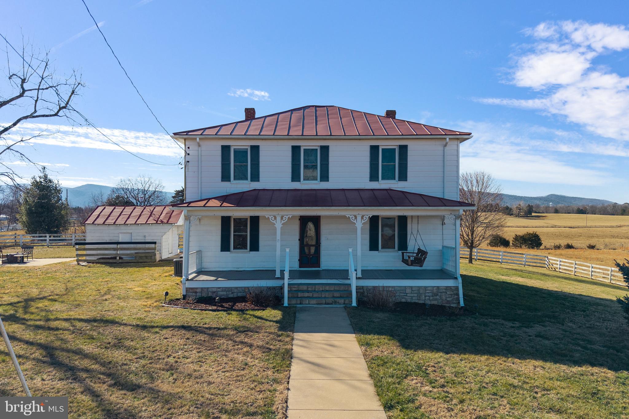 Modernized farmhouse on 4.7 acres with breathtaking Blue Ridge Mountain views. This 4-bedroom, 3-bath home blends historic charm with modern upgrades and features a grand center foyer with sweeping staircase. Spacious living areas include a gourmet kitchen with walk-in pantry, formal dining room, living room, office, and cozy family room. The primary suite offers a private bath and walk-in closet, while additional bedrooms are generously sized with abundant natural light. Outdoor features include a serene pond, covered front porch, rear patio with outdoor fireplace, and expansive mountain views. Three-bay detached garage provides ample storage and flexibility.