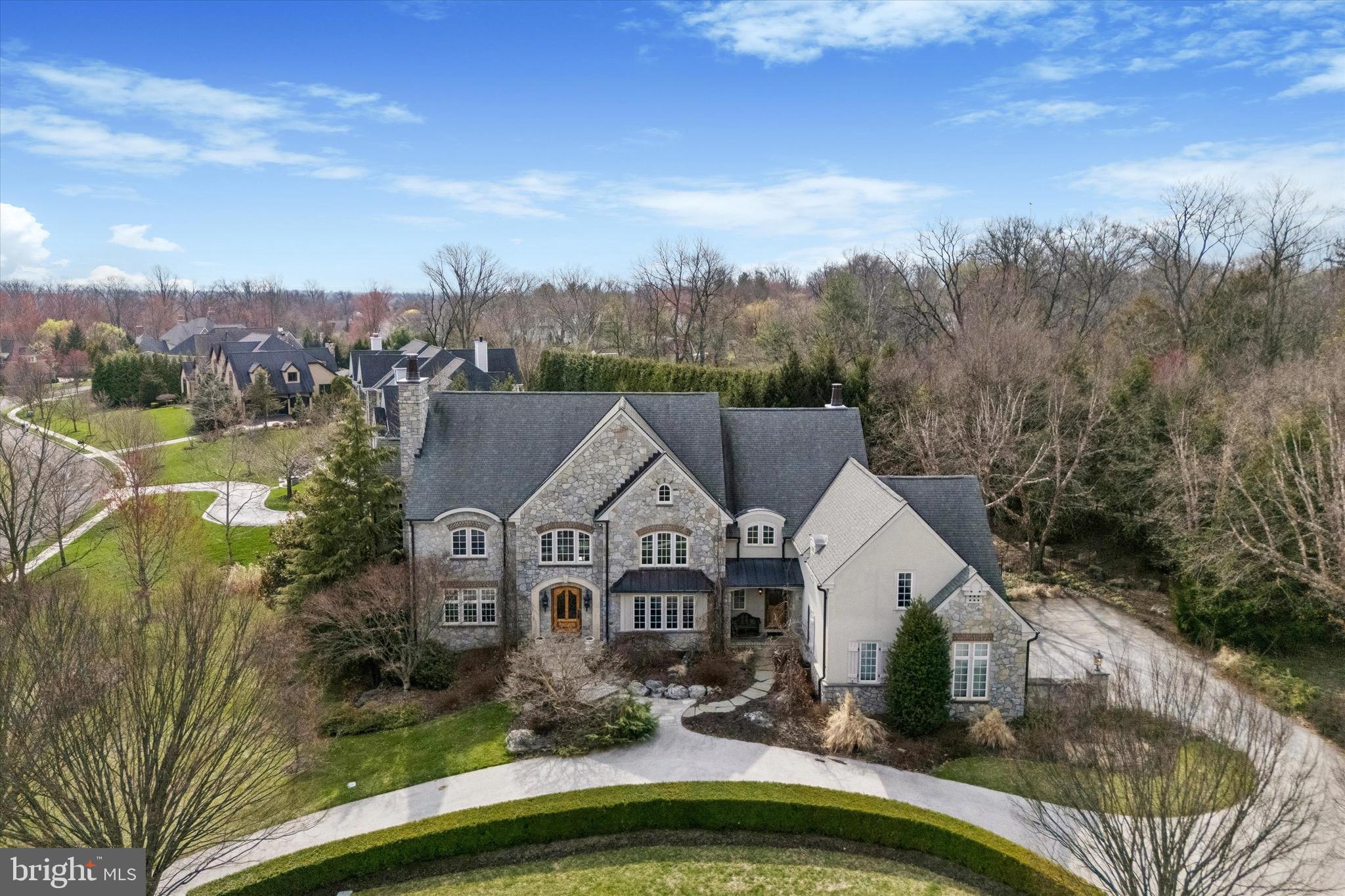 Step into timeless sophistication with this custom-built masterpiece by Parec, designed by renowned architect Rene Hoffman. Every detail has been meticulously crafted to seamlessly blend elegance and functionality, offering a luxurious yet practical lifestyle. With an elevator to all three levels and a spacious finished lower level with private access, the home is perfect for multi-generational living. From the moment you enter through the custom-designed front door into the breathtaking two-story foyer, you’re greeted by rich walnut hardwood floors, a sweeping staircase, and an open landing above. To one side, the formal living room exudes grace with intricate millwork, a gas fireplace, and French doors leading to a private office that features built-in cabinetry, a coffered ceiling with decorative beams, and terrace access. A second office—or potential fifth bedroom—offers abundant natural light, custom built-ins, and a shared powder room.  At the heart of the home lies a chef’s dream kitchen, complete with custom cabinetry, a granite-topped island, a raised walnut bar, and top-of-the-line appliances, including a six-burner Dacor cooktop, double ovens, and a built-in refrigerator. The sunlit breakfast nook opens to the terrace, while the adjoining family room impresses with cathedral ceilings, oversized windows, and a gas fireplace. A butler’s pantry with a built-in ice maker connects the kitchen to the elegant formal dining room, which boasts a tray ceiling and intricate molding. Additional features on the main level include multiple closets, a second powder room, and access to the attached three-car garage. Upstairs, the primary suite is a serene retreat with a cathedral ceiling, floor-to-ceiling windows, and two expansive walk-in closets with custom fittings. The spa-like en-suite bath includes a double vanity, soaking tub, tiled shower, water closet, and a dedicated makeup vanity. A coffee bar with a mini fridge and sink adds a touch of convenience. Three additional bedrooms include one with a private en-suite and two connected by a Jack-and-Jill bath. A versatile bonus room—or fifth bedroom—with roughed-in plumbing for a future bathroom and a second-floor laundry room with cabinetry, counters, and a sink round out this level. The fully finished lower level is an entertainer’s dream, featuring a temperature-controlled wine cellar for 775 bottles, a wet bar, a large recreation room, a cedar closet, abundant storage, and a full bath with a steam shower. With direct garage access, this space is as functional as it is beautiful.
Outside, your private oasis awaits. The lushly landscaped grounds feature stunning hardscaping, specimen trees, and a 20-zone irrigation system. At the heart of the backyard is a heated saltwater pool with a spa and waterfall, creating a resort-like ambiance. Thoughtful touches like extensive outdoor lighting make the space just as enchanting at night. Built to the highest standards, the home includes Pella architectural series windows, a CertainTeed Independence 50-year roof, copper gutters, and a whole-house generator. Located in the award-winning Wissahickon School District and minutes from premier shopping, dining, the Gwynedd Valley train station, and major transportation routes, this property offers unmatched convenience in a serene, private setting. This is more than just a home—it’s a lifestyle. Schedule your private tour today.