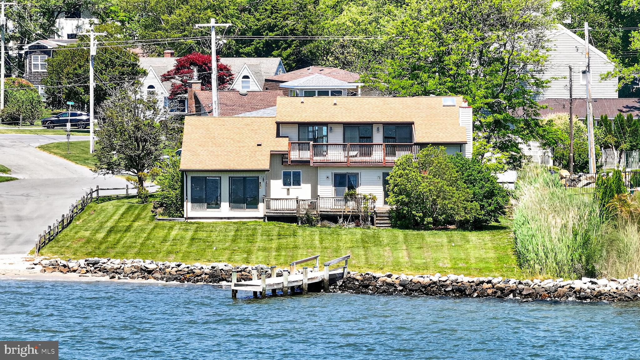 Welcome home to waterfront living in North Dewey Beach. Perched beautifully along the water’s edge in the highly sought-after community of Sea Breeze, this custom contemporary home offers a fantastic waterfront lifestyle. Boasting a rarely available bayfront setting on a generous 0.44-acre lot, this property combines thoughtful architectural design with the relaxed, unhurried rhythm of the Rehoboth Beach area. Featuring 3 bedrooms, 2 bathrooms, and 2,400 square feet of comfortable living space, the home is designed to maximize panoramic water views and natural light. Stepping inside, you are greeted by a bright, spacious, and open interior layout characterized by hardwood flooring and neutral paint tones. The main level features an impressive great room, where large glass sliders showcase the shifting colors of the water. Highlighted by a large brick fireplace and designed for seamless flow, it is the ultimate gathering spot for family evenings and casual entertaining. A nearby flexible den provides versatile space tailored for a private home office, a playroom, or a quiet haven for relaxation. The heart of the home is the bright kitchen, boasting crisp white cabinetry, matching appliances, and an abundance of counter space. Designed with an open layout and enhanced by subtle recessed lighting, the kitchen transitions easily into the adjoining dining areas, ensuring you are always part of the conversation. The sun-drenched dining room features a large slider overlooking the deck and water, transforming everyday meals into scenic dining experiences. French doors from the kitchen lead to the tiled sunroom, the perfect place to enjoy your morning coffee and a summer breeze. Down the hall, you’ll find two well-proportioned bedrooms offering excellent closet space and a nearby hall bathroom complete with modern fixtures, vanity storage, and clean finishes. For absolute convenience, the main level also hosts a dedicated laundry room. Retreat upstairs to the spacious primary suite, a private sanctuary carefully positioned to showcase spectacular, uninterrupted water views. This comfortable space features its own direct access to the elevated deck, ample walk-in closet space, and radiant natural light. There is a separate flex space on this level that could work as a sitting room or even a second walk-in closet. The en-suite bathroom is fully appointed with a double vanity, a walk-in shower, and a separate soaking tub oriented to capture serene views of the rippling water. Out back the lush green grass of the rear yard rolls down to the waterfront, complete with a private dock providing direct access for boating, kayaking, and aquatic recreation. The community boat ramp is literally steps away, making water access a breeze! A spacious two-car garage and a wide driveway ensure plentiful parking for guests. Located only 3 blocks from the ocean and just a quick walk into downtown Dewey, 208 Salisbury St offers a rare combination of waterfront property and coastal convenience. Schedule your private showing today!