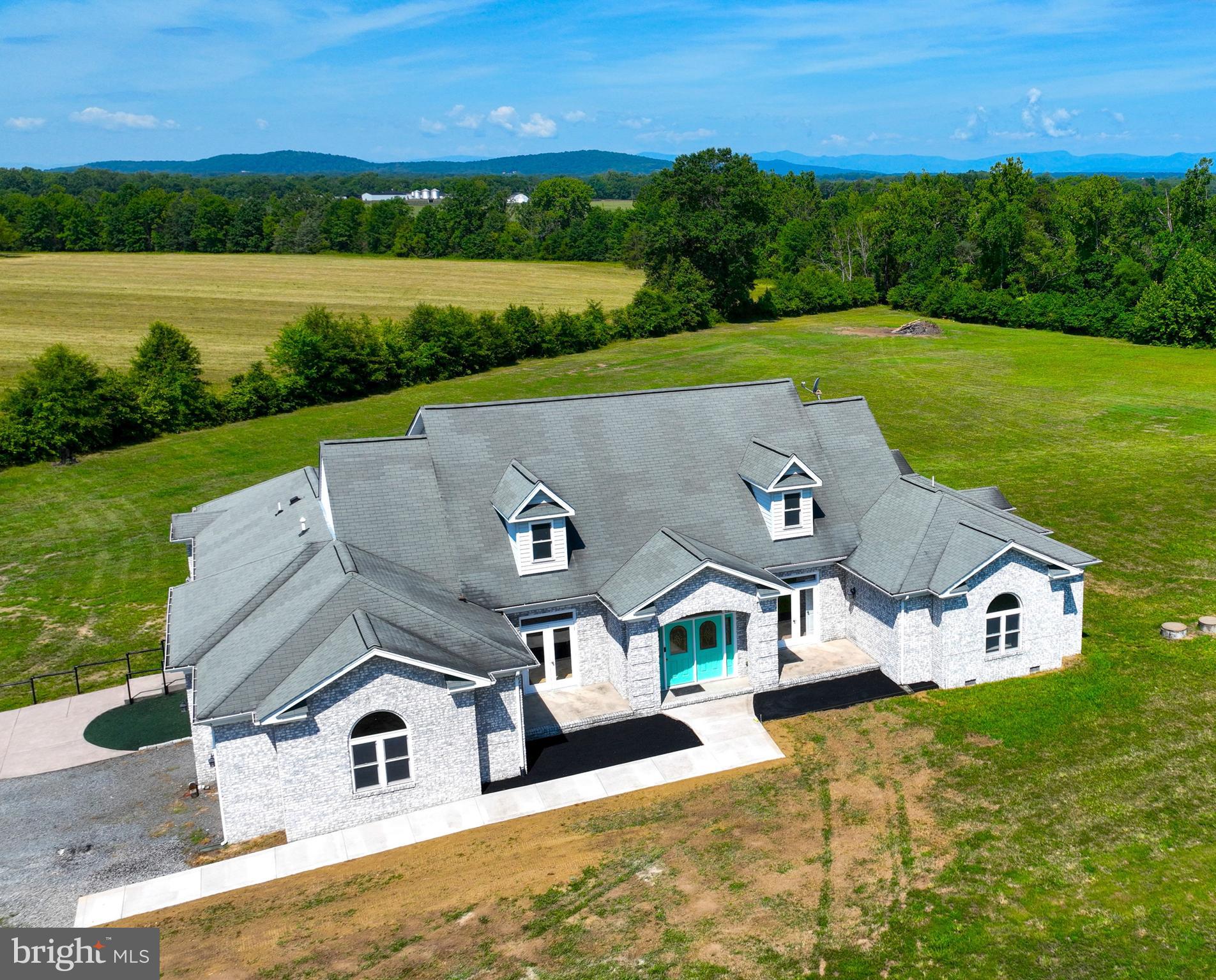 Welcome to this stunning custom manor home nestled in the heart of horse country in Culpeper County, Virginia! Only 10 minutes from town, this sprawling and rambling Shuman-built 4664 square foot main house sits on a lovely 65+ acre farm with endless possibilities...horse ranch, crops, or cattle.   Just minutes from world-renowned Commonwealth Equestrian Park, this property would be perfect for the horse enthusiast. Thoughtfully designed by the current owners...this all-brick home not only has 4 bedrooms with their own private baths, but also has fiber optic, 4 zoned HVAC systems, 4 gas fireplaces, crawl space with concrete slab flooring, 2 propane tanks,  120 gallon water heater, Everpure filtration system and Culligan water conditioner.  Step inside the ceramic-tiled foyer and be greeted by the warm ambiance of the living room's gleaming hardwood floors and comforting fireplace. Your family and guests will appreciate the elegance of the dining room that is tastefully framed by 4 ornate columns.  Meander to the huge kitchen that will surely be the focal point for any large gatherings. With "miles" of granite counter space, island and breakfast bar, feeding the masses is a snap with double wall oven, 5 Star gourmet gas range/hood and 2 sinks! The kitchen perfectly flows into the huge breakfast/dining area that comes complete with a mantled fireplace and plenty of sunny views of the surrounding land.  What truly sets this beautiful home from the rest is how the floor plan separates the "entertainment" wing from the "residence wing":  all bedrooms have their own full sized bathroom, with 3 of the 4 bedrooms are designed to function as separate suites.  The "Primary" suite has a private entrance to the rear patio,  a sitting/exercise room, 2-sided fireplace and a massive walk-through dressing room that connects to the amazing ensuite, which has a 2 head shower, circular jacuzzi tub and private water closet.  The second bedroom/guest suite also has a private bath, sitting/living room and fireplace. Upstairs is the third suite with 3 storage rooms, full bath and zoned HVAC that can also be used as a home office, game room or living quarters.  But wait, there's more!  Steps from the main home is the 2 bedroom guest home with den and 2 full bath has over 1600 sqft of living space and oversized garage. Designed for extended family members, guests, or use it for extra income!  Don't forget the massive 30' x 40' Morton workshop with 220 volt power, overhead lighting, and 8-inch concrete flooring that will support any equipment--or convert it to a horse barn. The land is suited well for nearly any agricultural/equine operation...plenty of space for paddocks, riding rings, buildings & pasture.  The land currently produces income and is in land use taxation for crops.  Whether you're an active farmer, equestrian, or need the perfect "compound," this estate offers the perfect blend of practicality, comfort and luxury.  Don't miss your chance to own this exquisite property in Culpeper - schedule a showing today!