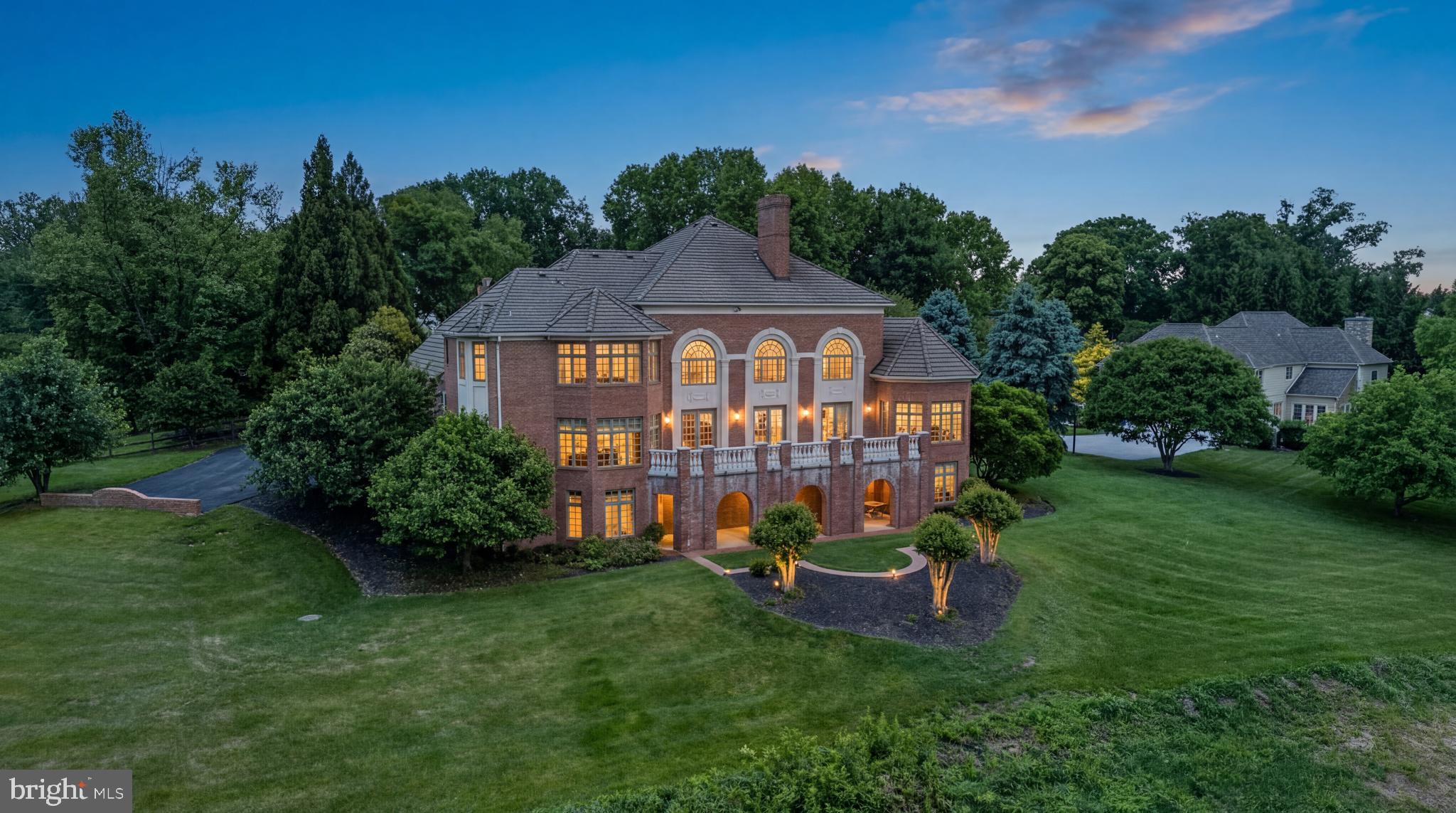 Privately set on 3.46 acres in Lutherville, 815 Hillstead Drive is a stately all-brick Georgian Colonial of exceptional scale, craftsmanship, and construction quality that is simply not replicated in today's market. A concrete slate roof rated for over 100 years and solid all-brick construction signal the standard this home was built to and has been maintained at. Nearly 10,000 total square feet across three fully finished levels, 6 bedrooms, 6 full and 3 half baths, a 3-car garage, and a 46-foot bluestone terrace with precast stone balustrade that opens to one of the most coveted views in Baltimore County: sweeping, unobstructed pastoral vistas across rolling private grounds and a mature tree canopy that stretch as far as the eye can see.
From the moment you step into the grand two-story foyer, the craftsmanship is unmistakable. Elaborate dentil crown molding runs the full perimeter of every principal room. Custom built-in cabinetry, floor-to-ceiling mahogany bookcases, and arched display niches are found throughout. The staircase and upper balcony feature solid turned wood balusters with a mahogany handrail that runs nearly the full width of the home, overlooking the great room below where the ceiling soars to approximately 20 feet. The entire rear of the main level, from the great room through the kitchen and sunroom, opens seamlessly to the bluestone terrace through multiple sets of French doors, bringing the pastoral views inside at every turn. The formal dining room, the mahogany-paneled office or library with its own fireplace, and a gracious formal sitting room offer the kind of room count that defines true estate living. The expansive kitchen features custom cabinetry, granite countertops, a full KitchenAid appliance suite, and a dedicated walk-in pantry just off the convenient laundry rom. The octagonal sunroom with floor-to-ceiling windows on all sides connects via a solid wood spiral staircase to the lower level. A main-level bedroom suite with private bath provides multigenerational flexibility from day one.
The primary suite is extraordinary: an octagonal tray ceiling with cove uplighting, a spa bath with marble floors, double vanity, soaking tub, and walk-in shower, and a his-and-her closet suite including a closet of over 650 square feet with vaulted ceiling and center island. Three additional upper level bedrooms each feature a private en suite bath, large closets with built-ins, and a Palladian arched window.
The lower level represents one of this home's most compelling opportunities. Thoughtfully designed as a complete, self-contained living suite with its own private entrance, full daylight throughout, and walkout access to the grounds through a signature all-brick arched exterior passageway, it is ideally suited for in-law living, an au pair suite, multigenerational arrangements, or extended guest accommodations at a scale and finish level rarely found. The suite encompasses a living room with fireplace, a formal dining room, a fully renovated kitchen with quartzite countertops and a KitchenAid gas appliance suite, a family room with bay windows and garden views, an entertainment room, a private bedroom, a full bath, a powder room, and nearly 750 square feet of dedicated storage, all served by its own private HVAC zone. Two separate interior staircases connect the levels seamlessly.
Major systems include a 5-zone HVAC system, propane boiler, private well with comprehensive water treatment, Generac generator and more, all meticulously maintained and updated over the years by original owners. Tucked away in total privacy, yet minutes from Greenspring Station, I-83, downtown Baltimore, and the area's finest private schools. A home of this construction, this quality, and this scale rarely comes to market. By appointment only.