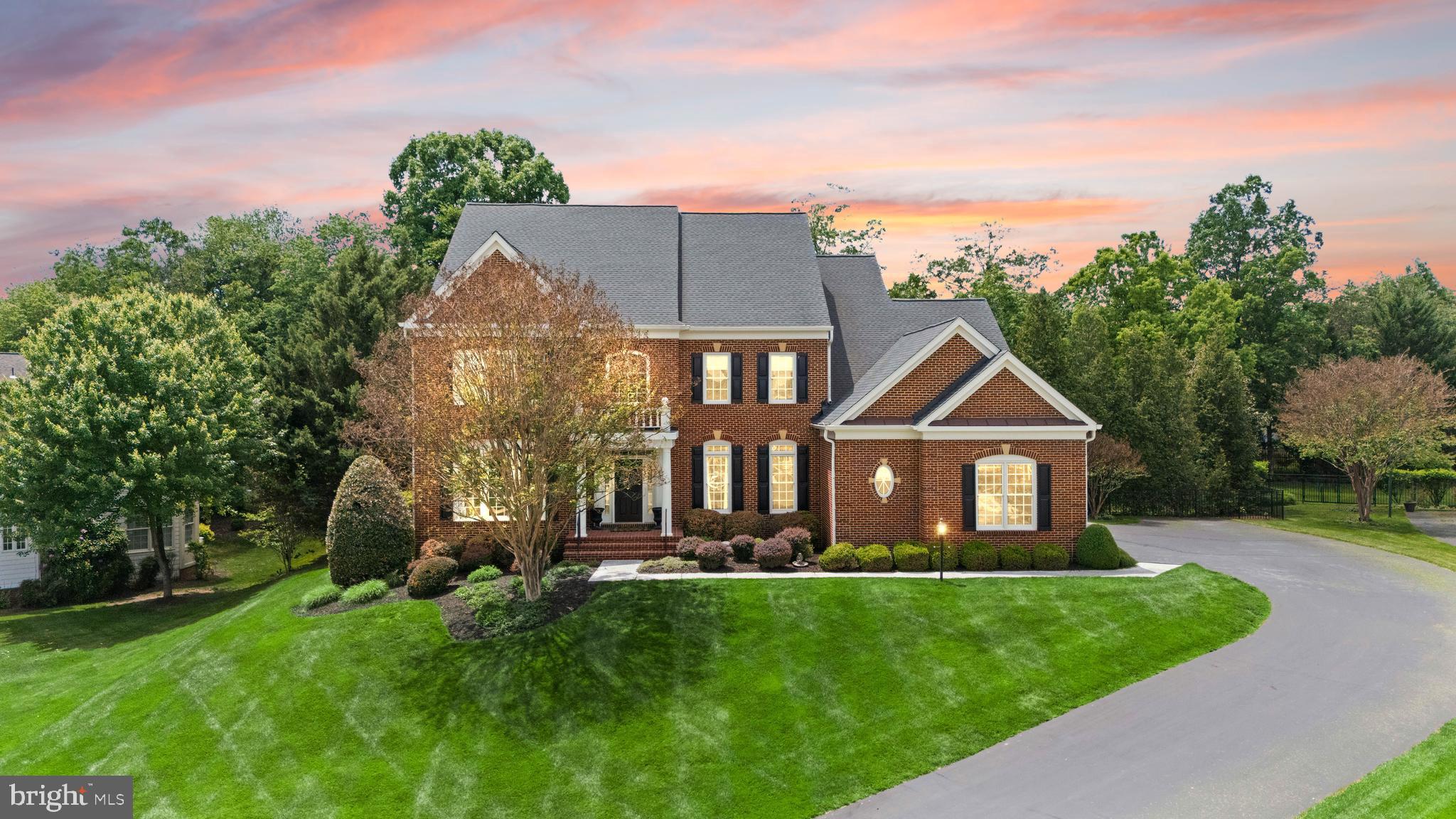 Open House Sunday May 31st 2pm-4pm**Refined Living in Lansdowne, Elevated. Set on a private horseshoe drive within the prestigious community of Lansdowne on the Potomac, this Lancaster model claims a rare half-acre lot framed by mature trees, with a depth of privacy that is truly rare. Extensive designer upgrades reach into nearly every room, headlined by a fully reimagined chef’s kitchen. Outside, a covered porch flows down to a sun-drenched pool, spa, and beautifully hardscaped grounds. Quite simply, one of the finest private retreats Lansdowne has to offer. Arrive on tree-lined streets to the stately brick-front Colonial facade, where a generous driveway opens to a three-car side-load garage. Inside, a light-filled foyer reveals a dramatic curved staircase, with formal living and dining rooms set on either side for entertaining or evenings in. French doors open to a private home office, where plantation shutters filter the incoming light. Throughout the main level, refinished hardwoods, elegant moldings, designer lighting, and curated wallcoverings strike a balance that feels at once timeless and current, while a redesigned powder bath adds a polished finishing touch. At the heart of the home, the chef’s kitchen is a natural gathering hub. White soft-close Shaker cabinets, refined brass hardware, undercabinet lighting, and glass-front displays meet a quality stainless appliance suite, including a Café range topped by a commercial-grade hood. The backsplash is understated and the quartz island a showpiece. The kitchen opens to an eat-in dining area, a Butler’s pantry with beverage fridge, and the family room centered on a floor-to-ceiling stone fireplace beneath a wall of windows that pulls the backyard inside. A mudroom with custom built-ins rounds out the main level. Outside, the covered porch is a destination in its own right, with a ceiling fan overhead for relaxed afternoons. Hardscape wraps the pool and spa, opening to a sundeck and patio with lush lawn beyond, all enveloped by layered privacy landscaping and mature trees. The result is a backyard that feels miles from anywhere. Upstairs, refinished hardwoods carry across the landing before yielding to plush carpeting in the bedrooms. The primary suite is impressive in scale, with a bay window framing tree views, a versatile sitting area, dual walk-in closets, and a primary bath featuring a corner soaking tub, oversized shower, and double vanities. A second en-suite bedroom offers its own full bath and walk-in closet, while two additional bedrooms share a well-appointed Jack-and-Jill bath. Below, the finished walk-out lower level adds another full floor of living. A spacious recreation room with deluxe wet bar opens directly to the pool area, joined by a dedicated workout room, a bedroom, and a full bath that together make for a polished guest suite or multigenerational setup. Over $250,000 in recent investments includes a new roof (2019), basement wet bar, bath, and gym along with custom mudroom built-ins (2021), custom kitchen renovation and refinished hardwoods (2022), new HVAC (2023), pool equipment and water heater (2024), washer (2025), and dryer plus bathroom updates (2026). Beyond the property, Lansdowne on the Potomac delivers an unparalleled package of amenities that includes indoor and outdoor pools, a fitness center, playgrounds, sport courts, aerobics rooms, business center, ballroom, meeting rooms, and more. Route 7 is moments away, along with shopping and dining at Lansdowne Town Center, the Golf Club at Lansdowne, Lansdowne Resort and Spa, One Loudoun, area hiking trails, and Bazil Newman Riverfront Park. For its location, lifestyle, and extraordinary privacy, this home stands apart.