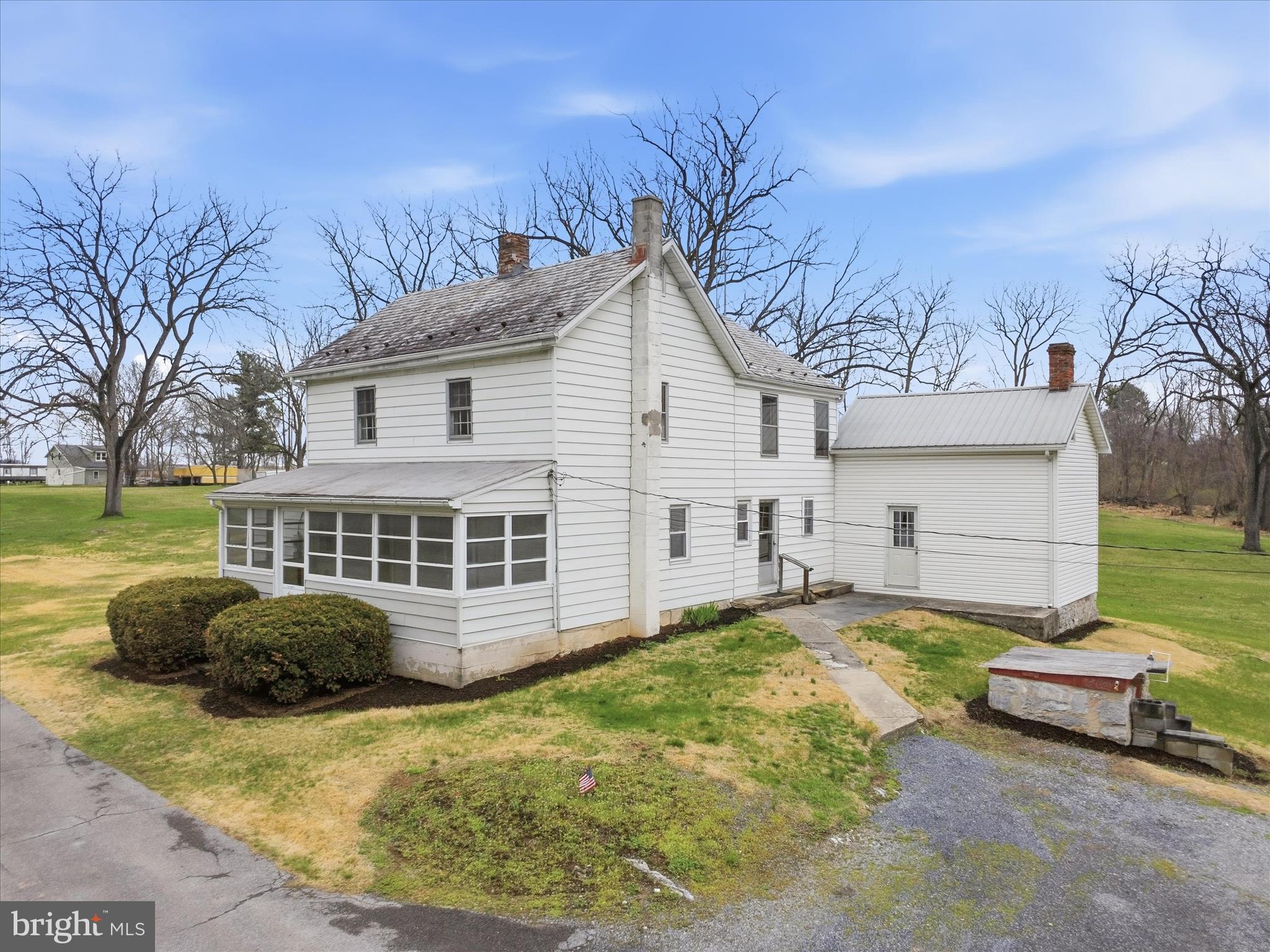 Welcome to 1376 Nolts Rd in Chambersburg, an incredible opportunity for homeownership. Conveniently located just minutes from the amenities of Norland Avenue and Walker Road, yet tucked away at the end of Nolts Road, this property offers privacy and lots of space on 4.29 acres.
With nearly 2,000 square feet of living space, this traditional 3-bedroom, 1.5-bath farmhouse offers character, charm, and versatility. The home features three enclosed porches, providing additional living space to enjoy throughout the year. The main level includes a large country kitchen with new vinyl flooring, and all kitchen appliances convey. The living room and family room feature new carpet, and a flexible office or potential fourth bedroom adds versatility to the main level. A first-floor laundry area and completely renovated half bath provide convenience for the homeowner. Upstairs, you’ll find three generously sized bedrooms with vintage wallpaper and linoleum covering original wood plank flooring, adding to the home’s character. The second level also includes a full bath and a playroom located in the enclosed upper porch. The home is heated by hot water baseboard heat on the main level, while the second floor contains floor registers but does not have an active heat source. The fully floored attic provides storage space or the potential to be finished for additional living area. Outside, the beautiful 4.29-acre setting offers endless possibilities for recreation, gardening, raising animals or simply enjoying your surroundings. The property features numerous mature walnut trees recently valued by a local forester at $16,500. Several outbuildings, including sheds, garages, and workshops, provide storage and ample workspace. Adjacent to the main house is a historic “wash house” built in 1896, formerly used as a summer kitchen, complete with a closed in fireplace and a second level. A former tenant house also remains on the property, but is currently uninhabitable. The property is serviced by an on-site septic system and private well, with a well pump that is just one year old. The home also features updated 100-amp electrical service. With its acreage, character, and multiple outbuildings, this property offers a rare opportunity to create the country homestead you’ve always envisioned. Bring your ideas and make it your own.
