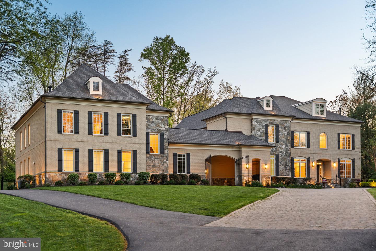 Gracefully positioned at the end of a private cul-de-sac on 2.12 manicured acres, this exceptional French Country estate with a private guest house and resort-style pool offers timeless elegance along the coveted Great Falls–McLean border within the Langley High School pyramid. Built by Keswick Homes, the residence spans 13,448 square feet and showcases soaring ceilings, Brazilian cherry hardwood floors, exquisite millwork, expansive windows, and a three-level elevator. A long private drive leads to a motor court and porte-cochère, setting the tone for the home’s impressive scale and craftsmanship. The chef’s kitchen is beautifully appointed with Sub-Zero, Wolf, and Miele appliances, dual islands, custom cabinetry, and seamless flow to the breakfast room and grand great room with a fireplace. Formal living and dining rooms and light-filled gathering spaces create the perfect balance of luxury and livability. The upper-level primary suite offers a private sitting room, fireplace, balcony, dual custom walk-in closets, and a spa-inspired bath. Of the seven total en suite bedrooms, five are found on this second level.  One primary-size suite, an independent wing of three generously proportioned bedrooms, one with a zero-entry shower with bench seating, extra-wide doorways, and wide hallway access to the elevator, ideal for multigenerational living. The expansive lower level features a media room, wet bar, billiards, recreation spaces, flex rooms, and guest accommodations. Outdoor living is truly spectacular with a 20x40 heated saltwater pool, retractable cover, outdoor kitchen with Viking appliances, stone fireplace pavilion, and over 6,000 square feet of Pennsylvania bluestone patios and covered porches. A detached 3,000+ square-foot carriage house includes its own kitchen, family room, two bedrooms, and a commercial-grade gym, creating an ideal guest residence, wellness retreat, or multigenerational living environment. Moments from Tysons, McLean, and Washington, this extraordinary estate offers privacy, scale, and resort-style luxury in one of the region’s most prestigious settings.