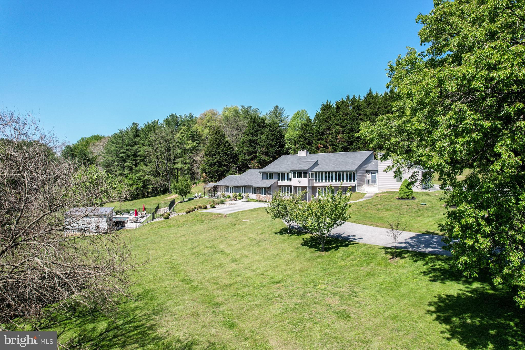 This extraordinary estate offers a rare blend of elegance, comfort, and versatility, perfectly designed for multigenerational living with seamless access to both levels of the home. Thoughtfully updated throughout, this residence showcases a commitment to quality and refined living.

At the heart of the home, the stunning, open-concept kitchen (2020) is truly a showpiece—anchored by an impressive 12.5-foot quartz island, complemented by a farmhouse sink, abundant seating, and picturesque views overlooking the beautifully landscaped grounds and sparkling pool. A walk-in butler’s pantry enhances functionality with a second refrigerator and dedicated wine storage, making entertaining effortless. 

Recent improvements include a new roof (2023), updated windows and siding (2015), primary bath (2020), a new well pump (2025), Main HVAC system (2025), and a premium Kohler whole-house generator with automatic transfer switch, providing peace of mind and uninterrupted comfort.  

Step outside to your own private retreat featuring a heated saltwater pool (2022) with an accompanying pool house—creating a resort-style atmosphere ideal for both relaxing and entertaining. The expansive 4.83-acre property offers breathtaking, serene views and ample space for gatherings, recreation, or simply enjoying nature’s beauty.

The main residence includes four generously sized bedrooms, with three conveniently located on the main level and a fourth on the lower level featuring abundant natural light and a private bath.  A truly special highlight is the private interior courtyard, a tranquil sanctuary perfect for yoga, quiet reflection, or intimate gatherings.

Immaculate, gleaming floors that reflect a true pride of ownership—beautifully maintained and move-in ready.

The separate in-law/au pair suite is equally impressive, offering a private one-bedroom layout with a den, one-and-a-half baths, full kitchen with quartz counters, laundry, and its own patio overlooking the scenic landscape. Designed with accessibility in mind, it features a zero-threshold shower for ease and comfort.

With its exceptional design, modern updates, and picturesque setting, this one-of-a-kind estate offers an unparalleled lifestyle—whether hosting unforgettable gatherings or enjoying peaceful everyday living surrounded by nature.