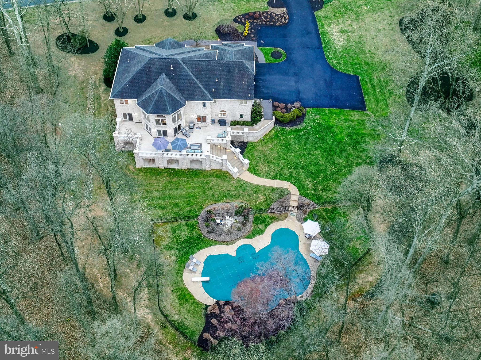 Live authentically. A stunning brick masterpiece nestled in the coveted enclave of Huntington in the heart of Caves Valley, this home is a private sanctuary embraced by lush woodlands. Meticulous landscaping frames the residence, where every space seamlessly flows to the great outdoors and an expansive terrace. Gather, imbibe and commune with nature... an outdoor space made to enhance your lifestyle. Bask in the serenity of nature or dive into the shimmering pool—an invitation to endless summer days of splashing and sun-soaked leisure. Floor-to-ceiling windows bathe the interiors with natural light. Thoughtfully designed living spaces blend sophistication with effortless functionality, from the gourmet kitchen that invites creating and sharing meals, to the grand dining room, poised to host unforgettable evenings. The magnificent owner’s suite offers a retreat of unparalleled tranquility, complete with a spa-like bath designed for indulgence with direct access to an epic dressing room. The finished lower level is a destination unto itself, featuring a restaurant-style bar, billiards area, and multiple guest suites... an entertainer’s dream. With direct access to the lower terrace, a wealth of inviting spaces await. Close to everywhere you want to be. Xfinity Internet. Cultivate your existence. The art of uniting human and home.