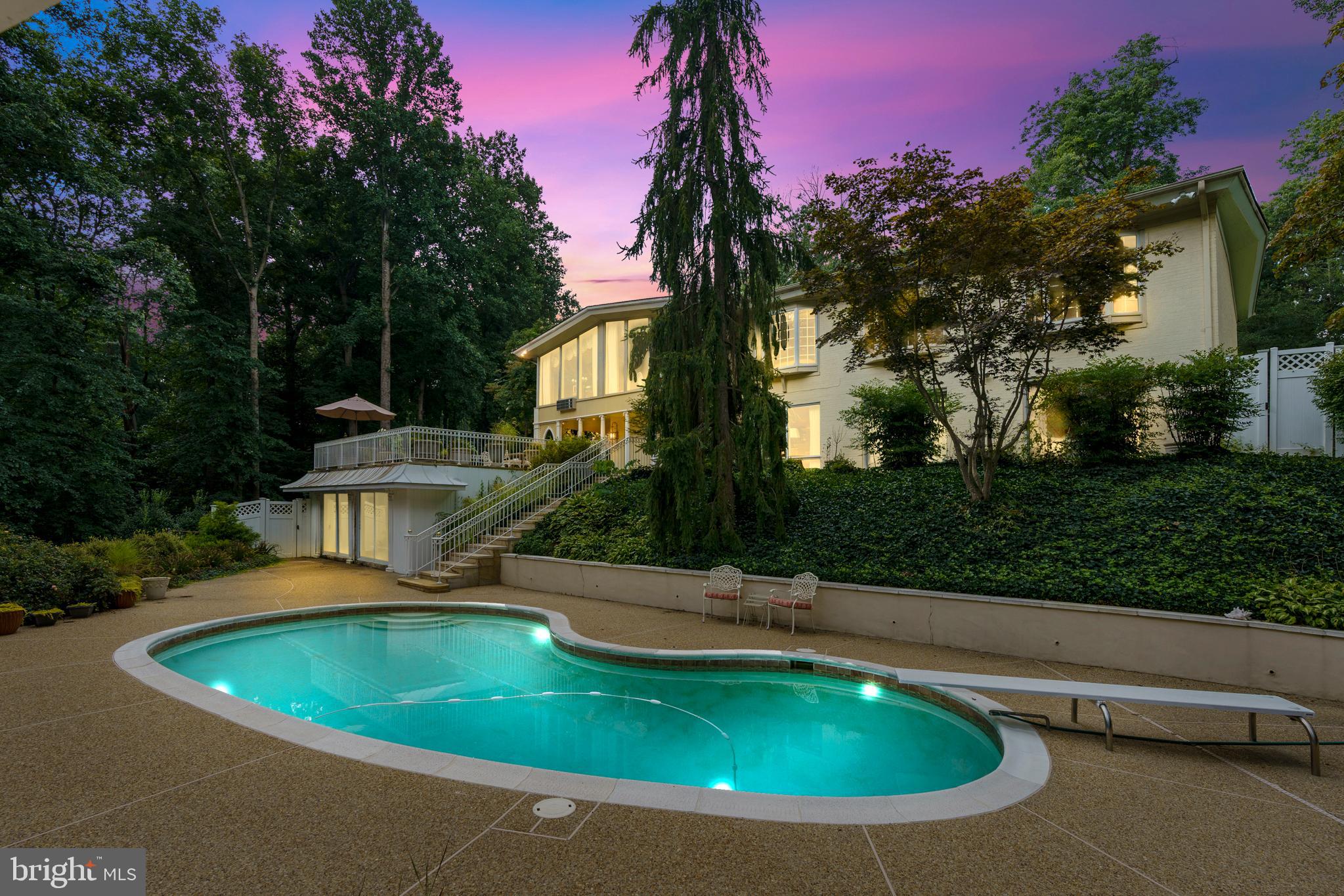 Never been available, this custom-built and designer-inspired home with a pool hits the market in Great Falls, VA! This home was custom designed ahead of its time in a Versailles detail and features 3 bedrooms, 2.5 baths, just over 3000 square feet of living space, 2 fireplaces, a detached 4-car garage, pool, bathhouse, gazebo, and separate studio/office all on 5.6 acres backing to Great Falls Park. The main level offers a welcoming foyer, which leads to the kitchen with high ceilings, custom architecture, floor-to-ceiling windows, and lots of storage. The formal dining room has room to seat 10. Enjoy a year-round sunroom with huge windows - you will feel like you are sitting in the trees! The formal living room is filled with natural light, coffered ceilings, and a stunning gas fireplace. A formal office with built-ins rounds out the main floor living area. Down the hall, a hall bath, the primary bedroom and bathroom, and the sitting room off the primary - convert this back to the 4th bedroom or it's perfect for a nursery, workout space, or additional office. The lower level is light-filled and has walk-out access in every room to the patio level. A spiral staircase down to the two bedrooms, a full bath, as well as a large recreation room with a wet bar and wood-burning fireplace, make it great for entertaining + easy access to the pool and decking. The laundry room and utilities also include a kitchenette, making it easy to entertain outdoors as it leads directly to that space. Multiple patios offer several areas to entertain and enjoy the private backyard. Down to the pool level and you will see a bathhouse with a jacuzzi tub, sauna, sink, and toilet - a blank canvas for your own spa or workout studio! Grab some sun in the wonderful gazebo overlooking the pool and into the woods. The pool retaining wall was recently reinforced. The large driveway, carport, 4-car garage, and parking lot area allow all of your guests to park on your property. The landscaping is mature and has been maintained meticulously. There is an on-site generator to provide storm coverage. The old barn on the property has been converted into a studio space and would make a wonderful office or art studio - let your imagination loose! The gorgeous 5.6-acre lot is filled with trees and you can even hear the falls when roaming through the trees. This property previously had horses and there is a horse run still on the lot. Located in the desirable Fairfax County School System; this home is zoned for Great Falls Elementary, Cooper Middle, and Langley High School. Minutes to 495 and major commuter routes. Just a short drive to Great Falls Village for shops, restaurants, and the library.