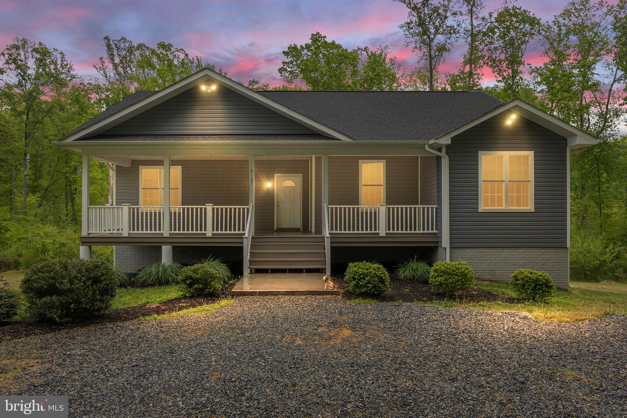 Custom built in 2020 and situated on 5.2 private wooded acres in Blount's Harbour, this Lake Anna water access home still shows like new. The long private driveway offers plenty of room for your RV, boat, and jet skis, and the 40-ft covered front porch sets the tone the moment you arrive. Inside, an open concept main level features 9-ft ceilings, luxury waterproof vinyl plank flooring, recessed lighting, and an electric fireplace. The kitchen offers granite countertops, a breakfast island with cooktop, and a dining area with views of the wooded backyard. The primary suite includes a large walk-in closet and a spa-style en-suite with dual vanities, porcelain tile, soaking tub, walk-in shower, and water closet. Two additional bedrooms and a full bath complete the main level. The walk-out lower level adds a large family room, full bath, laundry room pre-plumbed for a mud sink, and flexible office or storage space. Community amenities include a boat dock, pier, and picnic area. Xfinity high speed internet available. Minutes to Food Lion and less than 5 miles to Lake Anna restaurants, wineries, and activities. Four bedroom perc on file.