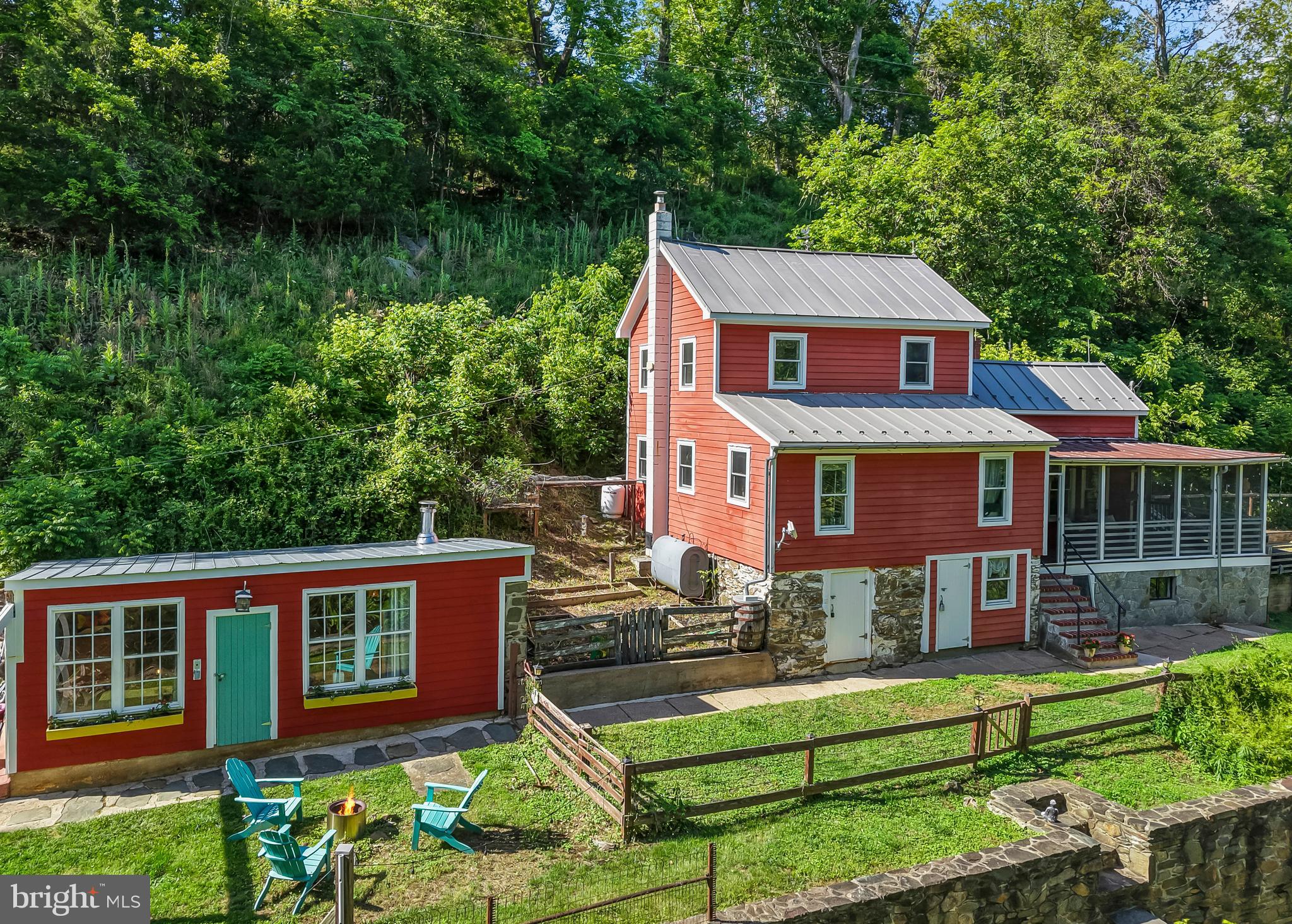 Rare opportunity to own a charming historic home nestled along scenic Catoctin Creek. Originally built in 1820, this unique property beautifully blends timeless character with the comforts of modern living. Whether you are searching for a peaceful full-time residence or a relaxing weekend retreat, this countryside gem in the heart of Loudoun County offers the perfect escape. An inviting front porch welcomes you into the bright and open kitchen featuring a raised beamed ceiling, white cabinetry, classic subway tile backsplash, and durable butcher block countertops. A cozy pellet stove efficiently heats the entire main level, complementing the oil baseboard heat. Conveniently located just off the kitchen is a combination powder room and laundry area. Just a few steps up, the spacious great room offers the perfect setting for dining and entertaining, complete with a wall of custom built-in bookshelves and warm wood flooring. The home features three bedrooms and 1.5 baths, with beautiful hardwood floors throughout. Two comfortable secondary bedrooms with closets are located just off the great room, while the upper level hosts a generously sized primary suite with a separate den or sitting room and a full bath. Adding to the property’s appeal, the current owners have thoughtfully expanded the usable living space by converting two outbuildings into a private office and a music studio, ideal for remote work, hobbies, or creative pursuits. Significant updates include four mini-split AC units (2020), concrete septic tank replacement (2021), new roof and HardiePlank siding (2015), and replacement windows (2014), offering peace of mind while preserving the home’s historic charm.