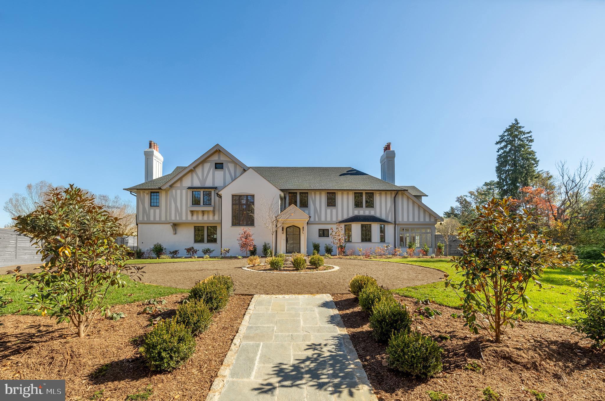 In the heart of Edgemoor, Bethesda’s preeminent residential community, is 7611 Fairfax Road, a faithfully reinterpreted Tudor estate blending the utmost in modern luxury with classical workmanship and tasteful architectural finishes. Sited on a 1/2 acre prime level lot, merely three blocks to Downtown Bethesda’s glass towers, the home represents a once-in-a-lifetime, no compromises opportunity. With prominent curb appeal, the facade evokes a sense of old world charm with its contrasting timbered trim and artful gables. The elegant arched glass and iron front door reveals an elegant reception hall and tucked away main staircase, introducing a reconfigured floor plan spanning a generous 7,600 square feet. In the nod to tradition, formal living and dining rooms flank the vestibule in a classic center hall layout. Both formal spaces are embassy-sized — the former spanning a full 30 feet in length — and feature roaring fireplaces. Off the living room is an intimate sunroom opening up to the grounds. In the center of the main level is a stunning chef’s kitchen with custom cabinetry and an imported commercial Italian oven. Stackable glass sliders open to reveal the patio and bring the outside in. Double doors part ways to reveal the main level primary suite’s private sitting room. The adjacent sleeping area features a soaring cathedral ceiling and offers direct outdoor access. The ubiquitous luxury amenities – marble-clad bath with dual vanities, freestanding tub, glass shower, enclosed water closet, and designer fixtures, as well as twin walk-in dressing rooms make the suite a secluded oasis. An expansive mudroom and access to the attached three car garage complete the main level. On the upper level is a second primary suite featuring a private fireplace and two truly expansive dressing rooms. Its ensuite bath mirrors the main level primary suite’s in both opulence and amenities. Three additional secondary bedrooms, each with ample closet space and marble ensuite baths, complete the upper level. A set of stairs accesses extensive storage space in the attic, while more storage space is provided in the lower level. During the transformation, the estate was taken down to the studs and contains all new HVAC, plumbing electrical, flooring, roof, and windows to establish a truly modern residence. Outside, nearly a half acre of flat, usable space affords expansive grass lawns and total privacy while remaining virtually unheard of in such a central location. Situated within walking distance to shops, restaurants, parks, entertainment and belonging to award-winning schools, 7611 Fairfax Road establishes itself as a leading estate in one of the Capital Region’s most sought after locations.