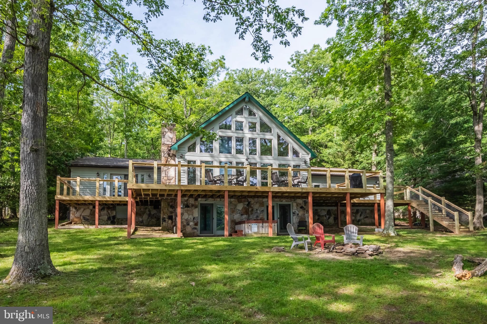 4BR, 4BA lakefront chalet with 124' of remarkably flat waterfront AND western exposure! Nearly one full acre in size, dockslip, big lake views inside and out, lakeside firepit,  3300sf home with over $200k in recent renovations. Impressive stacked stone fireplace. Recent upgrades: roof replaced  2 years ago, new 1400sf trex deck, updated kitchen, bathrooms, custom tile, flooring, updated furnishings and more!  Plenty of parking with an oversized, wrap-around driveway and attached garage. Excellent location on coveted Rock Lodge Rd. with deep water and on the main body of Deep Creek Lake. Established vacation rental 'Over the Rainbow'.