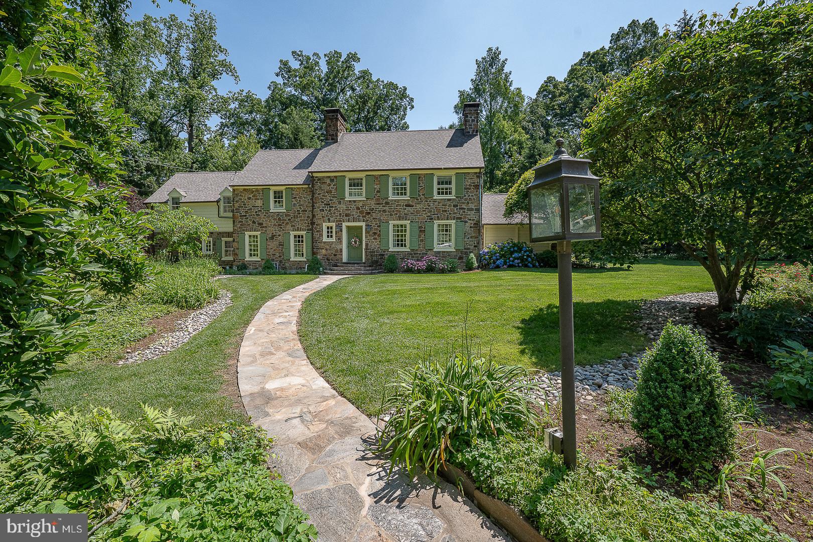Stately and beautiful, all hand-cut stone center hall colonial, sighted on an idyllic one acre lot with forested front lawn, located on one of the premier streets in Lower Merion. Architect John Lane Evans won multiple awards for his design, completed here in 1936. Radial stone steps up to portico and front door. Entrance foyer and center hall has coat closet and is 'straight thru' to back door, with stairs and powder room. Elegant, formal living room has prominent stone fireplace with a flagg hearth and built-ins with custom paneling. Cozy hideaway Library / Den lies beyond the LR, with second fireplace, custom paneling and built-ins. Den has bright and sunny glass atrium door for rear lot egress, and a charming water feature. To the left of the Foyer and center hall, step down into the formal dining room, with a third  fireplace, built-in china cupboards and a modern, glass window wall at the back, that opens to a private stone patio with electric awning. All of the formal rooms and foyer on the first floor have gorgeous and elegant random-width, hand-pegged hardwood floors. Dining room opens to both the Butler's pantry with sideboard and sink, and upper cabinets for glassware, and separately, opens directly into the cook's Kitchen, back stairs and breakfast room.  Eat in kitchen has breakfast nook, custom lighting, Corian counter tops with peninsula and sink at the side window. Double wall ovens, dishwasher and cooktop with custom tile backsplash complete the room.  Rear kitchen glass vestibule has back door to stairs, garage and driveway. Just off the Butler's pantry is a full bathroom and separate 4th family bedroom, currently in use as a WFH office.

Main stairs up to second floor landing, with hardwood floors throughout. Spacious owner's bedroom suite has large walk-in closet and 'retreat' sitting area. Bedroom is sunny and bright with six pretty windows, and has a full, private bath. Two additional, spacious family bedrooms share a second, full hall bathroom. Hall has additional linen and storage closets, along with back stair access.

Partial lower level is at grade, with 1.5 car attached garage, full laundry room with walk out to covered alcove and driveway and storage or play room with mechanicals.  Whole house natural gas generator.