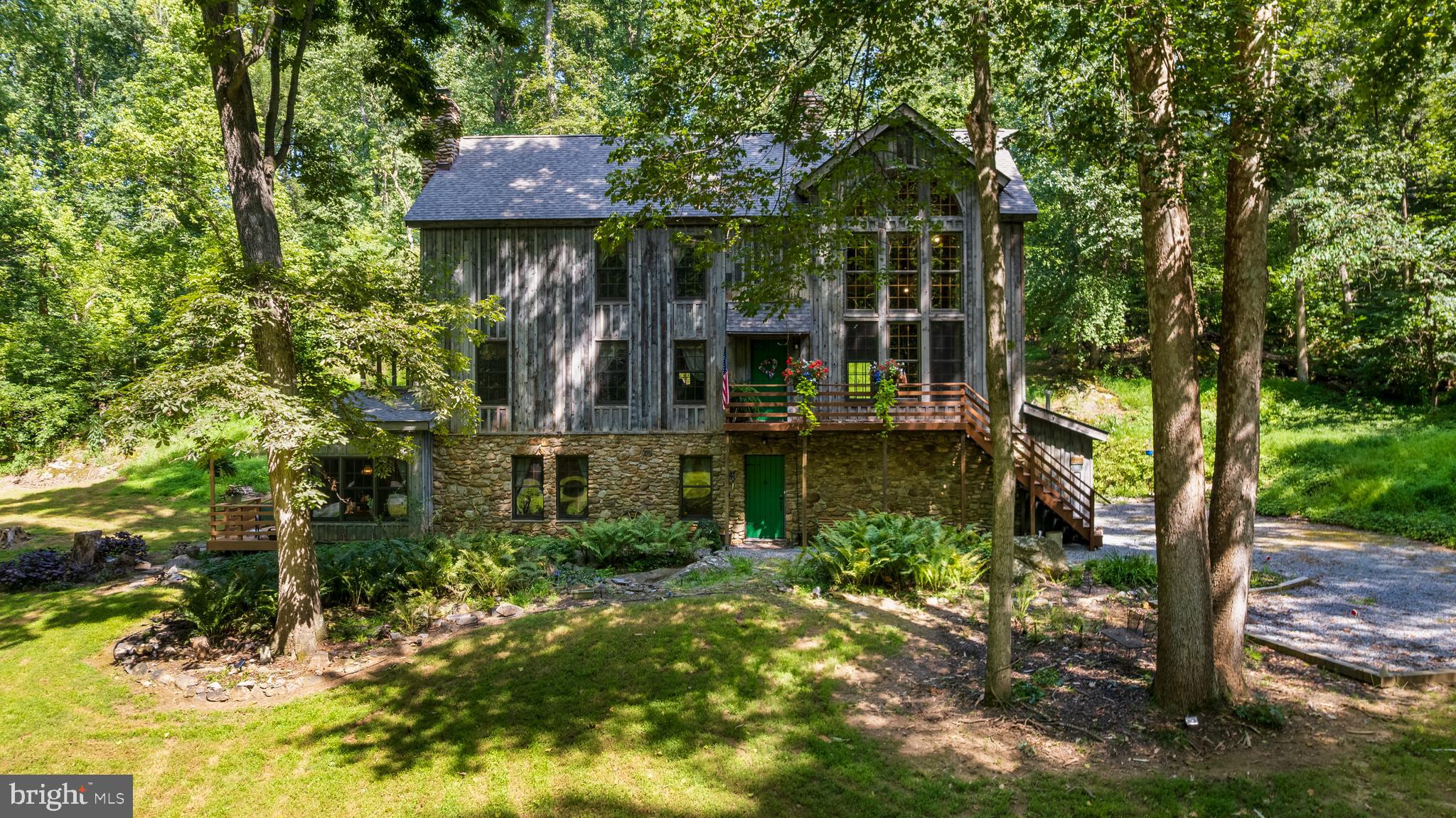 Just minutes from Shepherdstown on 2+ acres sits this distinctive custom Mill Creek Timber Frame home.  Built with craftsmanship and distinct attention to detail in 1993,  this timber frame home consists of 5 bedrooms and 3.5 baths.  The nicely landscaped grounds of mature trees and large rock breaks greet you as you enter the property and quickly lead you to the heart of the home - a soaring great room  anchored by vaulted ceilings, a grand window 22-foot high with natural stone outside and inside.   The great room fireplace rises to a beamed cathedral ceiling 27' high, with 2 x12'  wood plank flooring throughout, that flows into a country kitchen, dining room,  half bath, screened porch and deck that offer ample room to relax, entertain, and take in the surrounding tranquility.

Three cozy bedrooms make up the sleeping spaces of this home.   The true charmer is the elegant primary suite which offers generous closet space and bathroom complete with separate vanities and large jacuzzi tub.  The primary bedroom extends to a 10 X 32 loft for exercise room, crafts, sewing and  additional closets.

The ground level full apartment features 2 BR, full bath, kitchen/dinette, deck, stone fireplace, separate  entrance, and a fire pit.  Suitable for in-laws,  family, multigenerational, Airbnb, or to rent out.
All cabinets, doors, and closets are custom handcrafted by "Little Cove
Furniture."   Rounding out this unique property is the spacious, detached  550 sq. ft. matching building uniquely designed with workshop, storage, and space for lawn equipment that provides endless potential for a studio or easily converted into additional living space.   

This is the property to relax and watch nature!!!  Conveniently located minutes from the vibrant culture, dining, shops, and historic charm of Shepherdstown plus convenience to the Potomac River, C&O Canal, Antietam National Battlefield, Shepherd University, National Conservation Training Center, Cress Creek Country Club, Bavarian Inn Resort, nearby MARC Train, and so much more.