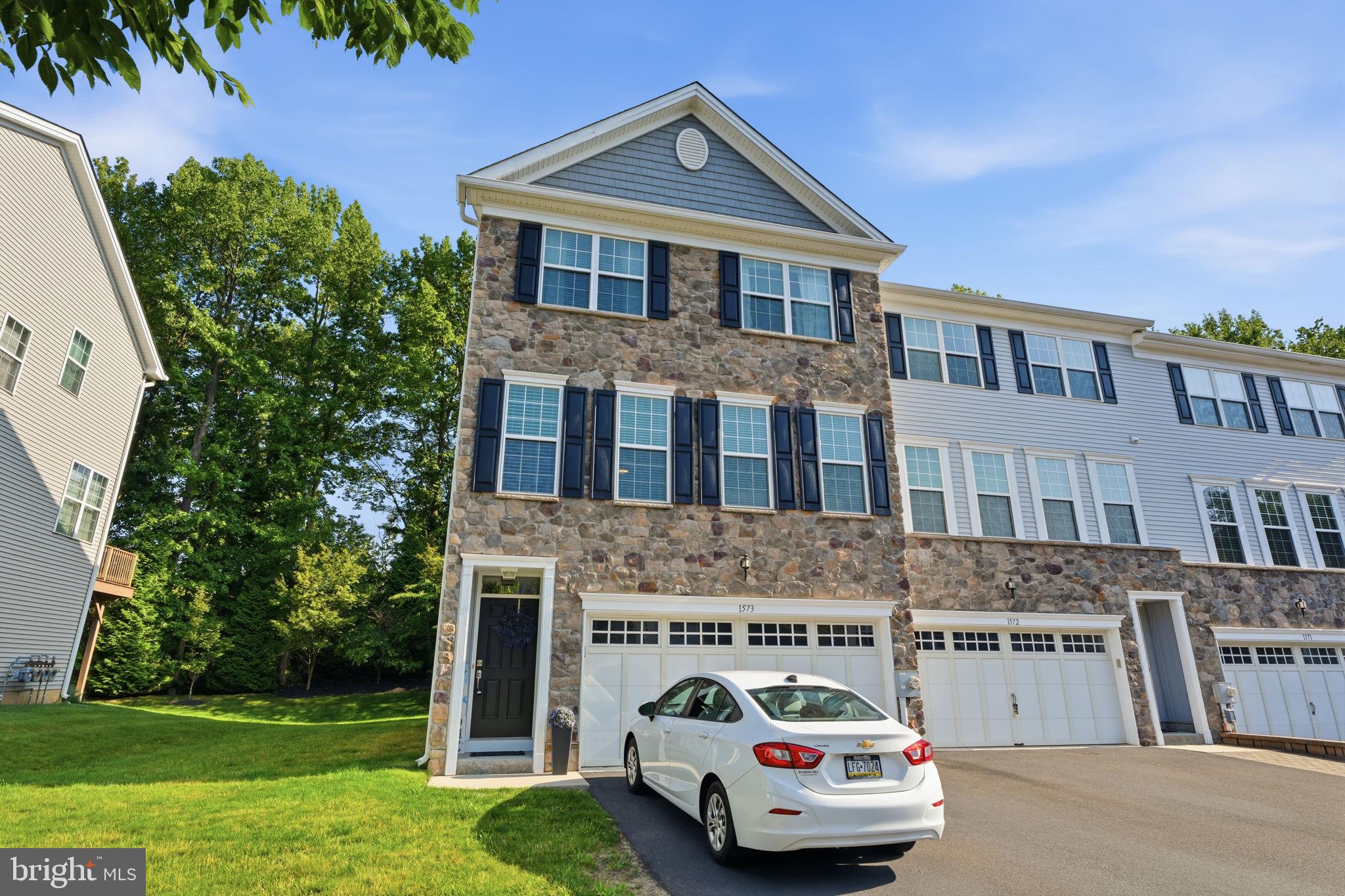 Welcome to this impressive 3-bedroom, 2.5-bath Middleberry model, an end-unit carriage-style townhome offering 2,287 square feet of living space in desirable Big Oak Crossing. An attractive fieldstone façade, paver walkway, two-car garage and driveway parking for multiple cars create outstanding curb appeal.
The ceramic-tile entry opens to a bright, spacious interior enhanced by recessed lighting, upgraded windows, six-panel doors and decorative crown molding, chair rail and picture-frame molding. The open-concept main level is ideal for everyday living and entertaining. The sleek kitchen features stylish 42-inch cabinetry, granite countertops, stainless-steel appliances, a double oven and a large center island. The adjoining dining area is filled with natural light from an oversized sliding glass door with transom window and provides access to the elevated deck. A spacious living room completes this inviting level.
Upstairs, the generous primary bedroom features an attractive tray ceiling and large walk-in closet. The private primary bathroom offers an elegant ceramic-tile floor, tiled shower surround and dual-sink vanity with granite countertops and backsplash. Two additional well-sized bedrooms provide ample closet space, while the conveniently located upper-level laundry adds everyday ease.
The sunny lower-level family room features nine-foot ceilings and offers flexible space for recreation, a home office, fitness area or media room. A sliding glass door provides direct access to the backyard. Additional highlights include abundant storage, a high-efficiency heating system, 200-amp electrical service and interior access to the two-car garage.
Big Oak Crossing is a well-located, low-maintenance community featuring attractive open spaces and walking and biking paths. Enjoy convenient access to Core Creek Park, shopping, dining and entertainment throughout Langhorne and the Oxford Valley area. Commuters will appreciate proximity to Route 1, I-295 and the Pennsylvania Turnpike. Located in the Neshaminy School District, with current assignments to Core Creek Elementary School, Maple Point Middle School and Neshaminy High School. This beautifully designed end unit combines generous living space, modern amenities and an exceptionally convenient Bucks County location.