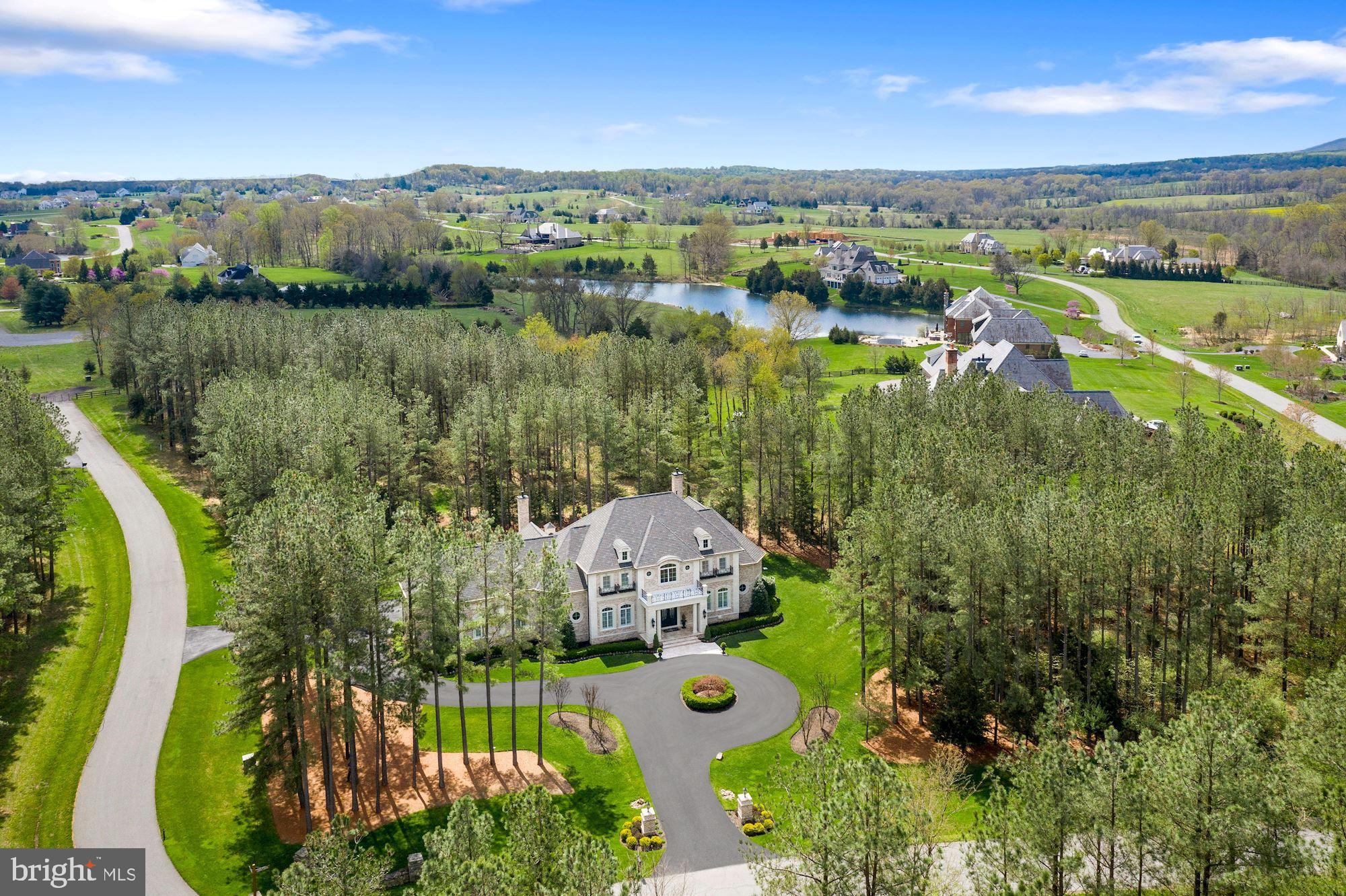 Prepare to fall in love with this spectacular custom-built home behind the gates of the private, award-winning Creighton Farms Country Club community. You will feel as though you have entered the grounds of Augusta National when you arrive at this pristine French Manor Estate featuring nearly 10,000 finished SF on 3+ pine tree lined acres, meticulously landscaped, with dramatic landscape lighting. Dual entry driveways with a circular drive will guide you towards the elegant iron gate front doors, leading you into the stately two-story Foyer with soaring 25’ ceilings, a sweeping and floating solid wood staircase with iron spindles and views of the Romeo & Juliet balconies on the upper level. Luxurious appointments throughout include French-Travertine chiseled-edge flooring, 8” reclaimed hardwood floors, designer chandeliers to include many by renowned Luxe designer, John Richard, an integrated whole house interior/exterior audio visual, top of the line security with 24-hour exterior surveillance/video recording, 4-zone HVAC, Generac whole house generator, maintenance free gutter system, whole house water softener and reverse osmosis water purification system in the Kitchen. The Gourmet Chef’s Entertaining Kitchen boasts a professional grade Wolf 60” gas double oven and range with six burners, double griddle and wall-mounted pot-filler, 9.5’ island complete with Wolf built-in microwave and warming drawer, Bosch dishwasher and abundance of under island storage. Custom designed inset furniture grade raised panel cabinetry with 56” upper cabinets is complimented by Sub-Zero refrigerator/freezer and 8’ range hood decorative surround. The Sun Room has beautiful 16’ cathedral ceilings, gas fireplace and wet bar. An Art Gallery hallway with 6 pre-lit Art niches to showcase your most prized pieces directs you to the Executive Office and highly desired main level Owner’s Suite, with 16’ cathedral ceilings, tailor designed His and Her Owner’s closets, an opulent Owner’s Bathroom with Calcutta marble flooring/surround, a seamless shower with dual shower heads and a lavish air jet bubble soaking tub. The Great Room features 25’ coffered ceilings and fireplace with large marble mantel, also boasts a floor to ceiling wall of windows allowing sun drenched natural light overlooking the backyard Oasis with an oversized Travertine patio, built-in seat wall, custom lighted Pavilion with 5-seat bar, 9’ resort style firepit, 12’ masonry gas fireplace and two covered porches. A 3-bay dream garage with 14’ ceilings can accommodate up to 6 cars with the installation of car lifts. The basement begins with a French styled 1,000+ bottle, temperature-controlled stone wall encased wine cellar and personal wine tasting area! Enjoy the 120” grey screen in your state-of-the-art Theatre. Floor to ceiling stone fireplace in the Rec Room. Game and Club Rooms feature an 8' American Heritage professional pool table and 16' handcrafted bar. Spacious Guest/Au-Pair Suite with private exterior entrance for total privacy, a finished storage room and a hidden concrete and steel reinforced Safe Room with extensive built-in custom cabinets is there for you to discover on your tour of the home!! Creighton Farms is one of greater Washington DC’s most extraordinary, exclusive private club communities. The crown jewel at Creighton Farms is the 18-hole Jack Nicklaus championship golf course. Unparalleled resort style amenities include a brand-new state of the art golf facility with heated indoor bays, two Har-Tru & two USTA hard-surface tennis courts, fitness & wellness facilities, a resort style pool and an elegant Club House offering indoor & al-fresco dining, overnight club rooms for members and guests, Board Room, Library, Golf Shop & more. Please take our video tour through the following link https://www.youtube.com/watch?v=tAJofmrzMKs