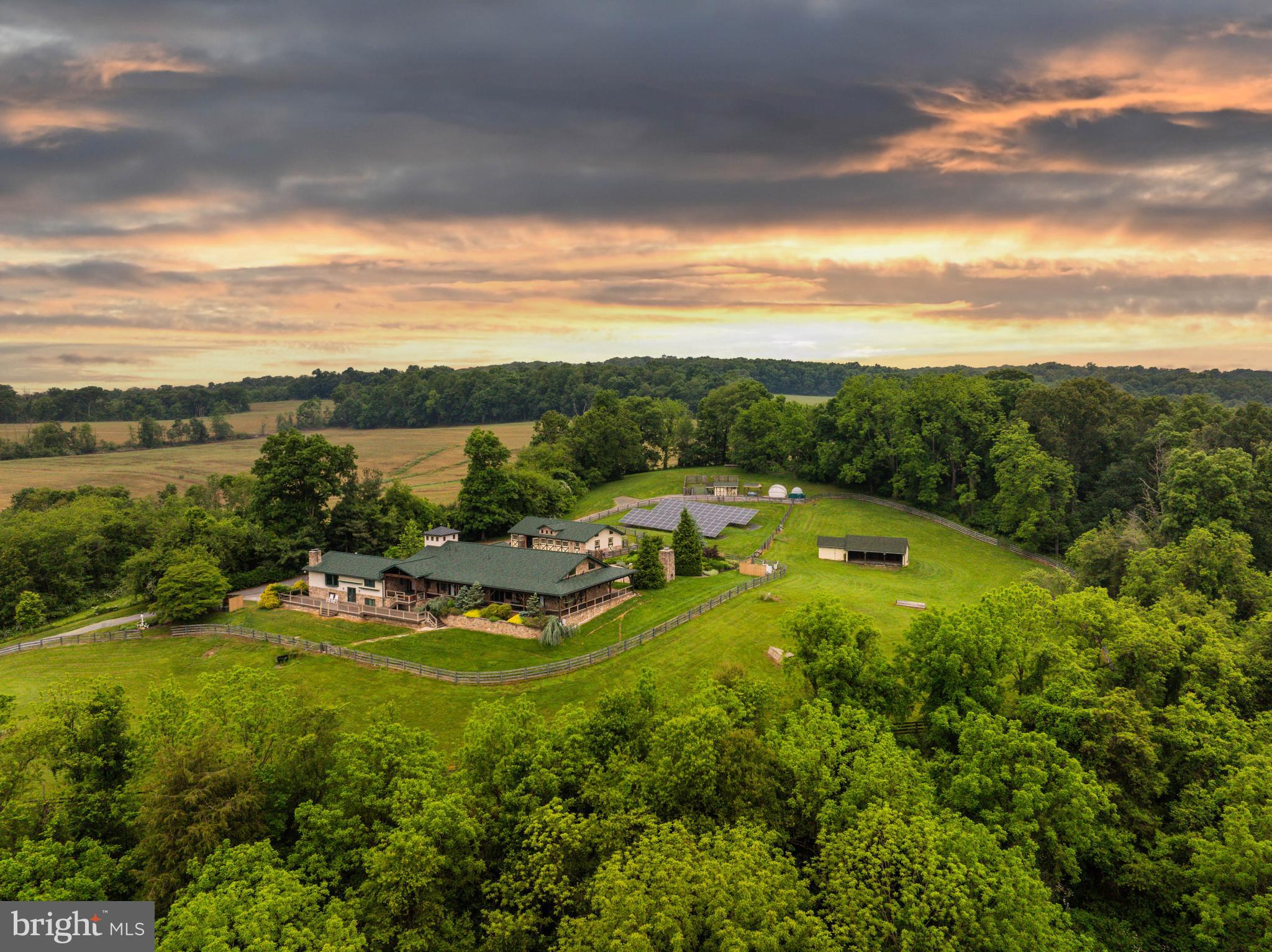 Live authentically. Cedar Crest Farm. Discover a sanctuary where authenticity meets tranquility. Embrace the road less traveled and look forward to meandering through serene country lanes, enveloped by towering trees, leading you to your haven. You have arrived at your equestrian estate. Channeling an enduring Jackson Hole Mountain aesthetic, perched on 19.67 enchanting acres with panoramic big sky views...you won't want to leave. 
Be greeted by a soothing neutral palette and exquisite millwork that showcases superior craftsmanship throughout. Expanses of glass and open spaces frame the beauty surrounding you. Step outside to a 140-foot wraparound covered loggia that terraces to an elaborate 80-foot-long incredible deck, perfect for taking in breathtaking sunsets and sunrises. Enjoy leisurely evenings under the stars on your stunning terrace. The tranquil fountain sculpture, "Coming Together", by Aristides Demetrius, is as remarkable as it is soothing. Let scintillating conversation flow freely by the cozy fireplace and inviting fire pit—ideal for gatherings and quiet reflection alike.
Behold the party barn of all party barns. Three stories of jaw-dropping exposed beams, soaring ceilings and a plethora of possibilities. Complete with its own kitchen, bath and dedicated bedroom space.
For the riding enthusiast, there's an impressive 200x90, 18,000 square foot indoor riding arena where the lights come on instantly. There are mirrors covering the back wall and the walls are canted for safety. No detail is overlooked. The footing is a comfortable mix for horses including bits of tire. Ride effortlessly from the indoor to your outdoor riding arena, complete with jumps and jump storage. There is also a full cross-country course on the property. This includes coops, bank jumps, tables, corners and everything a rider desires. Eight stalls in the bottom barn, one of them currently used as the wash stall equipped with hot and cold water and heat lamps. The upper barn offers a multitude of possibilities due to its spacious and versatile nature...it currently has two stalls. Ample garage space at the house and down at the barn could make an easy conversion to more stalls if needed. The hay shed holds 500+ bales of hay. Ideal for anyone looking to enjoy and utilize a well-equipped equestrian facility, whether for personal use and beyond. Additional features include run-ins and an accessible stream through the bottom fields with a charming bridge. Indulge in luxury with a lap pool and hot tub, providing year-round relaxation and wellness. The lush greenery encircling the property enhances the sense of seclusion and peace. This property is not just a farm, but a lifestyle—a place where every day feels like a retreat. Cultivate your existence. The art of uniting human and home.