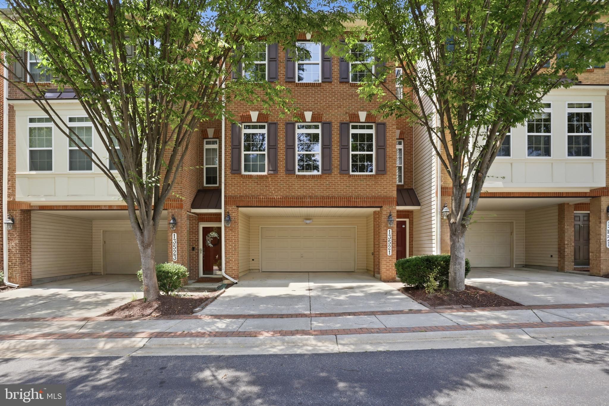 Welcome to 13521 Latrobe Lane, an exceptional luxury townhome nestled within the highly sought-after Gateway Commons community of Clarksburg. One of the largest models available, this elegant brick-front residence showcases timeless architecture with a stately portico entrance, two-car garage, private two-car driveway, and an impressive presence that immediately sets it apart. Step inside to bright, sun-filled interiors where brand-new paint and plush new carpet create a truly turnkey experience. Ascend to the expansive main living level where rich hardwood flooring, extensive crown molding, chair rail detailing, designer chandeliers, recessed lighting, and oversized vinyl-clad double-pane windows combine to create an atmosphere of refined sophistication. The formal living and dining spaces offer the perfect backdrop for entertaining, seamlessly flowing into a stunning gourmet chef's kitchen featuring 42-inch snow-white cabinetry, gleaming granite countertops, stainless steel appliances, a gas-powered range, designer backsplash, upgraded refrigerator with ice maker, abundant cabinetry, and generous prep space for gatherings of any size. Just beyond, the inviting family room centers around a cozy gas fireplace with an elegant mantle and opens to a private balcony—an ideal setting for morning coffee, outdoor dining, or evening grilling. Upstairs, retreat to an extraordinary owner's sanctuary highlighted by soaring cathedral ceilings, two expansive walk-in closets complete with custom closet systems, a separate sitting area, designer chandelier, and a luxurious spa-inspired ensuite bath featuring a frameless glass shower, relaxing soaking tub, granite double vanity, 42-inch snow-white cabinetry, elegant pendant lighting, private water closet, and linen storage. Two generously sized secondary bedrooms with brand-new carpet and paint, a beautifully appointed full bath with ceramic tile and tub/shower combination, and a conveniently located upper-level laundry room complete the bedroom level. The entry level offers additional flexible living space with recessed lighting, walkout access to the private patio, mechanical room, and direct access to the oversized two-car garage. Significant recent improvements include upgraded hardwood flooring on the main level, brand-new paint, brand-new carpet, a new HVAC system (2026), new dishwasher, stove, and microwave (2024–2025), new washer and dryer (2024), and an upgraded refrigerator (2020), providing exceptional peace of mind for years to come. Beyond the home, Gateway Commons delivers an outstanding lifestyle with beautifully landscaped parks, scenic walking trails, playgrounds, fountains, and abundant green space, all while placing you just moments from the renowned Clarksburg Premium Outlets, countless restaurants, grocery stores, fitness centers, and everyday conveniences. Ideally situated immediately off I-270 with easy access to Rockville, Gaithersburg, Frederick, and Washington, this remarkable residence offers the perfect blend of luxury, convenience, commuter accessibility, and low-maintenance living in one of Montgomery County's most desirable communities.