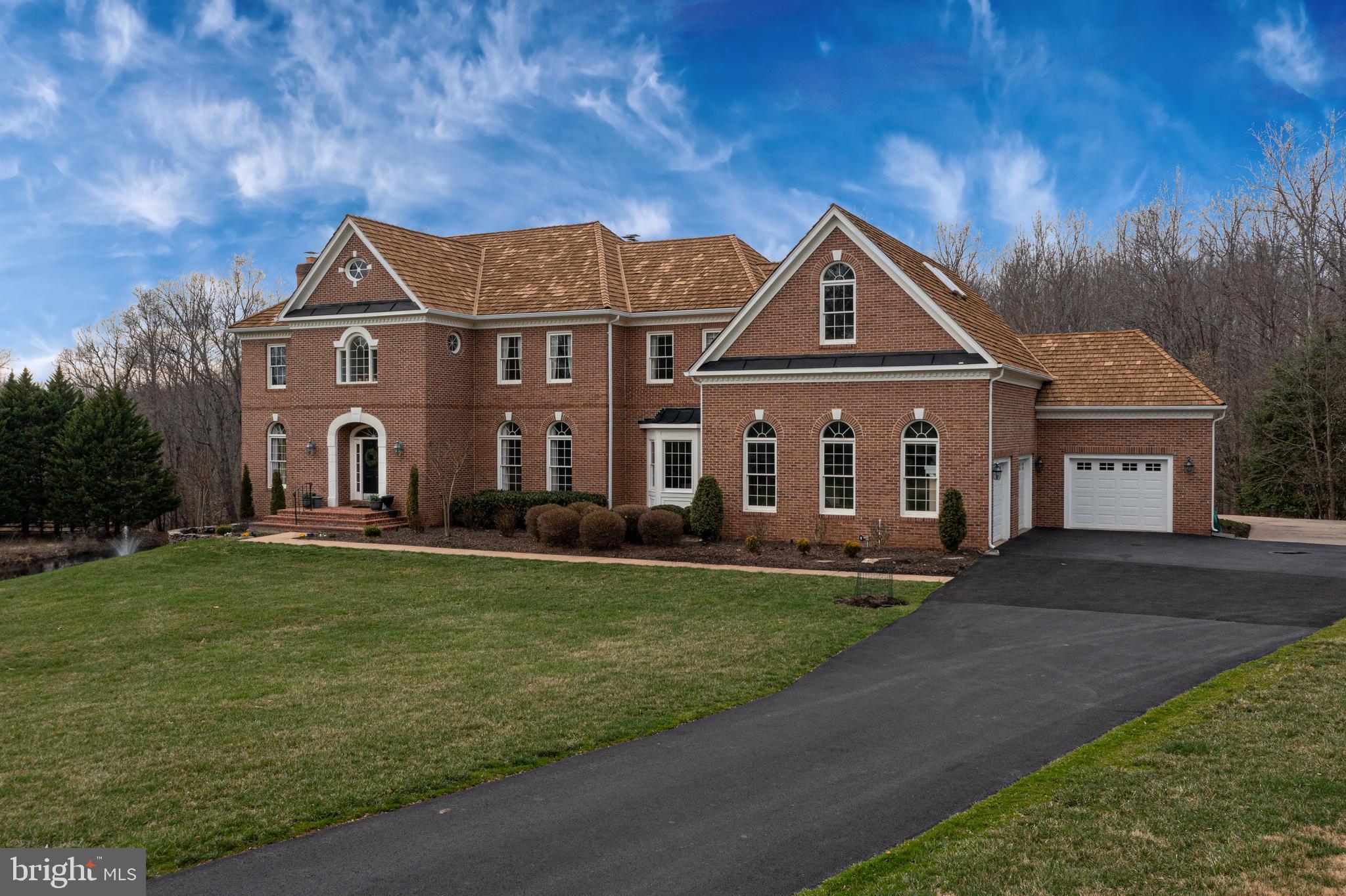 This stunning  5.83 acre Fairfax Station home boasts 8 bathrooms , 5 bedrooms and a 3  car garage .  It is situated on a beautiful piece of land in Hampton Hunt Estates with its very own pond and fountain.  The interior has a pleasing open floorplan with 5 fireplaces and 2 staircases.  There is hardwood throughout the top 2 levels and updates galore!  Step into the marble foyer to be wowed by the curved staircase and the spacious great 2 story great room ahead of you with its impressive view and tall palladium windows and  2 story gas fireplace.  A sunny formal living room  with a wood-burning fireplace is also on this level along with a large office complete with distinguished built-ins and French doors to the balcony which runs along the entire back of the home. This home has one of the most impressive dining rooms which you have most likely ever viewed. Ample space for huge parties and large crowds to entertain. The extra ordinary kitchen is impressive with its gas stove, additional ovens,  warming drawer, huge fridge, 2 dishwashers, 2 sinks and an extra large island and a separate walk-in pantry too!  This main floor has two fully updated half baths along with a second large study room and a large laundry/mud room full of built-ins.  Moving upstairs you find a large master bedroom suite with 2 sitting areas, another gas fireplace, a second laundry  and an opulent master bathroom complete with 2 chandeliers, custom built-ins, multiple closets and a custom dressing room to enjoy! Each of the other 3 bedrooms have their own fully updated bathrooms too.  Downstairs you get to enjoy the most recent updates of this gorgeous home! Here you find the 5th bedroom, along with a walk-in closet and a full bathroom. This can easily be used as an in-law or au pair suite with its own outside entrance, large full kitchen, laundry hook-up & eating & sitting area. The downstairs also has two exercise rooms, along with a take-your-breathe- away large recreation room with a white stacked stone gas fireplace, custom built-in bar, climate controlled wine cellar & another fully updated 1/2 bath. This walk-out basement has a gorgeous view of the pond & fountain & you can thoroughly enjoy the large exterior patio too. If you love suburban amenities, but  want the privacy of your own large private retreat with easy commute options you will fall in love with this home!  This home has 3 HVAC units (2011, 2017 and 2022) along with 2 Hot Water Heaters & a cedar shake roof which was just given a preservation treatment in 2022. Welcome home!