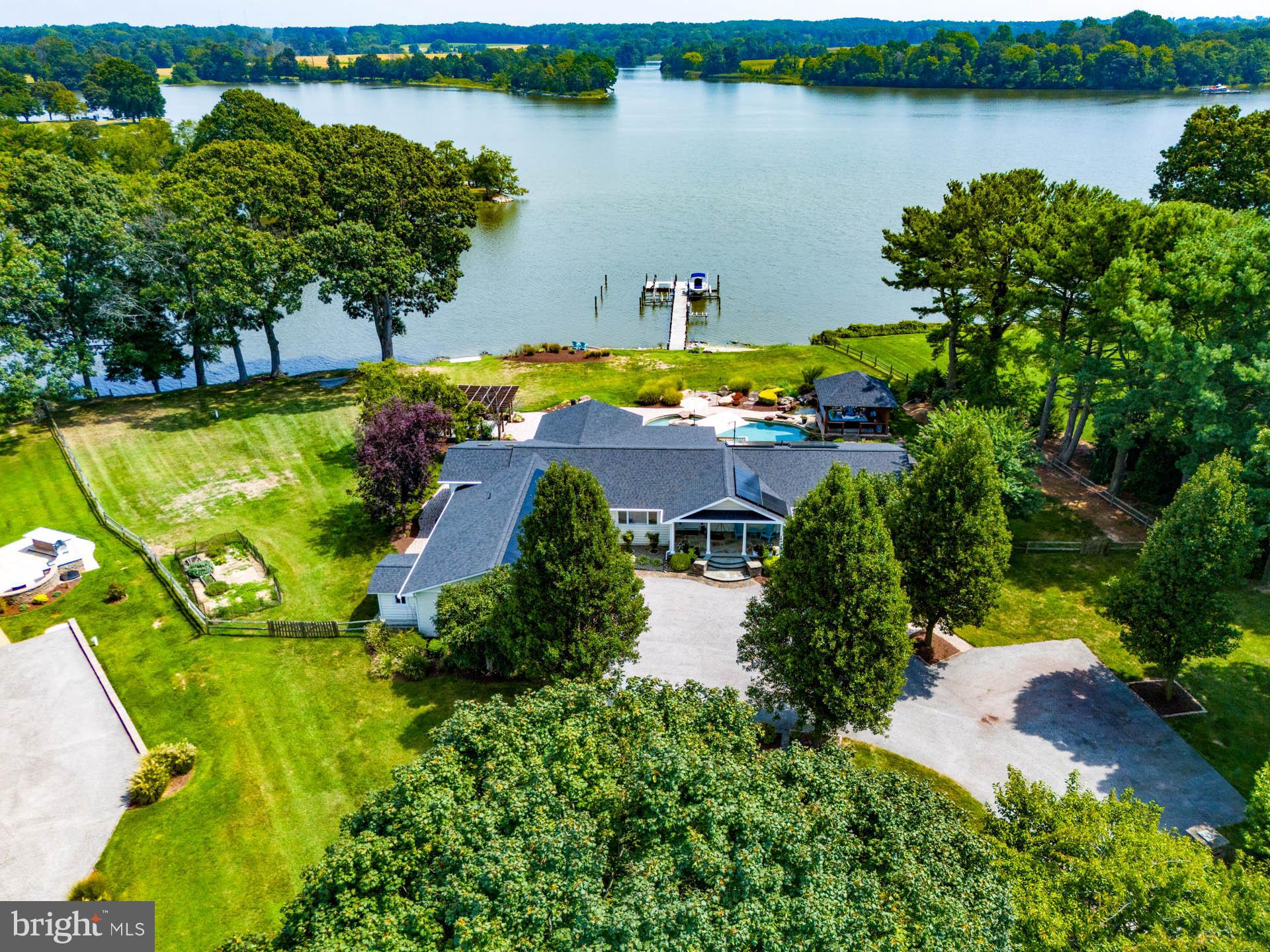 Waterfront Oasis on The Wye River. This incredible home is completely turnkey with large open floor plan and incredible views from virtually every room. There is a family room with a gas fireplace, a separate River Room with 3 walls of glass, private dining room, sunroom, and office. Fabulous kitchen with seating at the large island, stainless appliances, quality cabinets, soft close drawers, lovely granite counters, gas stove, 2 ovens, and walk-in pantry. Primary bedroom with private renovated bathroom, large walk-in closet with custom shelving system, plus sliders to deck where the hot tub is only a step away. Lower level with 4th bedroom and a dedicated new high-end bathroom, plus large family area and wet bar. Resort-like backyard has extensive hardscaping, multiple decks, unbelievable pool with stone features/waterfall, pergola, and covered outdoor stone fireplace with a grilling station. The owner installed a new roof (2023) and solar panels (owned) so there are virtually no utility bills! Pier with lifts on 5-6' MLW, boat ramp, sandy beach, paved driveway with lots of parking space & 2-car garage.