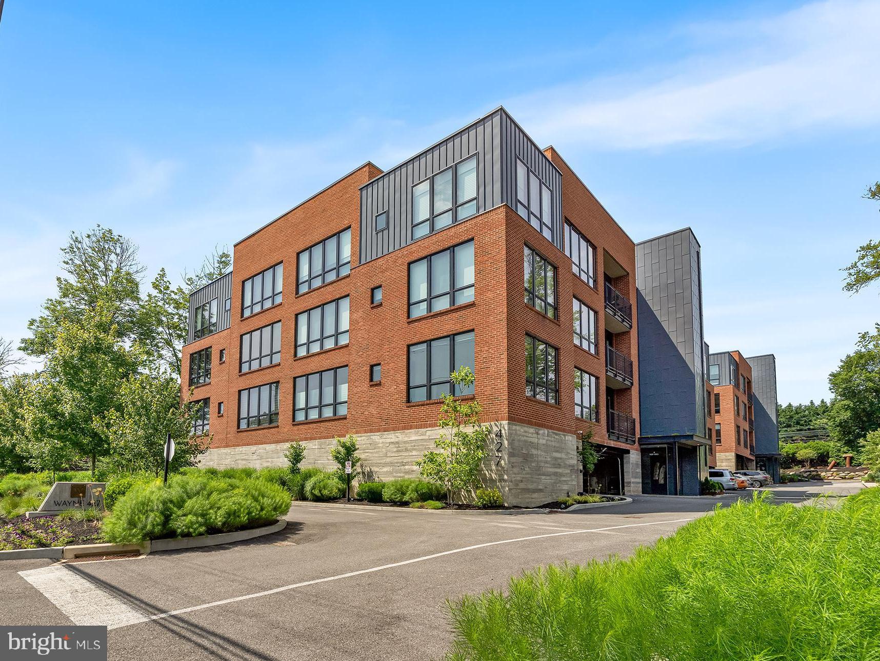 Upscale Luxury and elegance converge at Wayne 427, this 3-year-young condominium is a quick walk to the heart of downtown Wayne’s bustling activity and train. This stunning 2-bedroom, 2.5-bath residence offers 1,880 sqft of designer living space, an abundance of sleek high-end finishes, state-of-the-art technology, and amenities, including wide plank oak hardwood floors, soaring ceilings, a private balcony, and oversized windows that frame tranquil tree-top views. The open-concept layout is anchored by a sophisticated living and dining area, complete with a stunning gas fireplace featuring a dramatic custom floor-to-ceiling marble surround, designer light fixtures, and automatic shades. The chef’s kitchen is a showpiece, boasting an extended waterfall edge quartz island with seating for 4, designer backsplash, custom cabinetry, floating shelves, and premium Bosch stainless steel appliances, gas 30” 5 burner cooktop, a Range hood and XO wine fridge—perfect for entertaining in style. Off the kitchen glass French doors open onto your own private balcony overlooking the tree tops.
The expansive primary suite includes a custom outfitted walk-in closet and a spa-inspired bath with a double vanity, radiant heated floors, a soaking tub and frameless glass-enclosed marble shower. A second en suite bedroom with corner windows provides flexible space for guests or a home office, this bedroom has a custom outfitted closet and a luxurious bath. 
This chic condo is accessed through keyless entry, where you are welcomed into a beautifully appointed lobby that sets the stage for this unique luxury building and the common spaces that are designer finished, featuring large windows and tall ceilings. Enjoy modern conveniences like secure electronic entry, two deeded garage parking spaces, exclusive access to building amenities including a fitness center, a serene garden courtyard, a green roof, a dog run and beautiful plantings all along the property, and each unit has its own storage unit, and there is ample guest parking.
All just steps from Wayne’s premier dining, shopping, train station, and located in the award-winning Radnor School District—this is maintenance free elevated Main Line living at its finest.