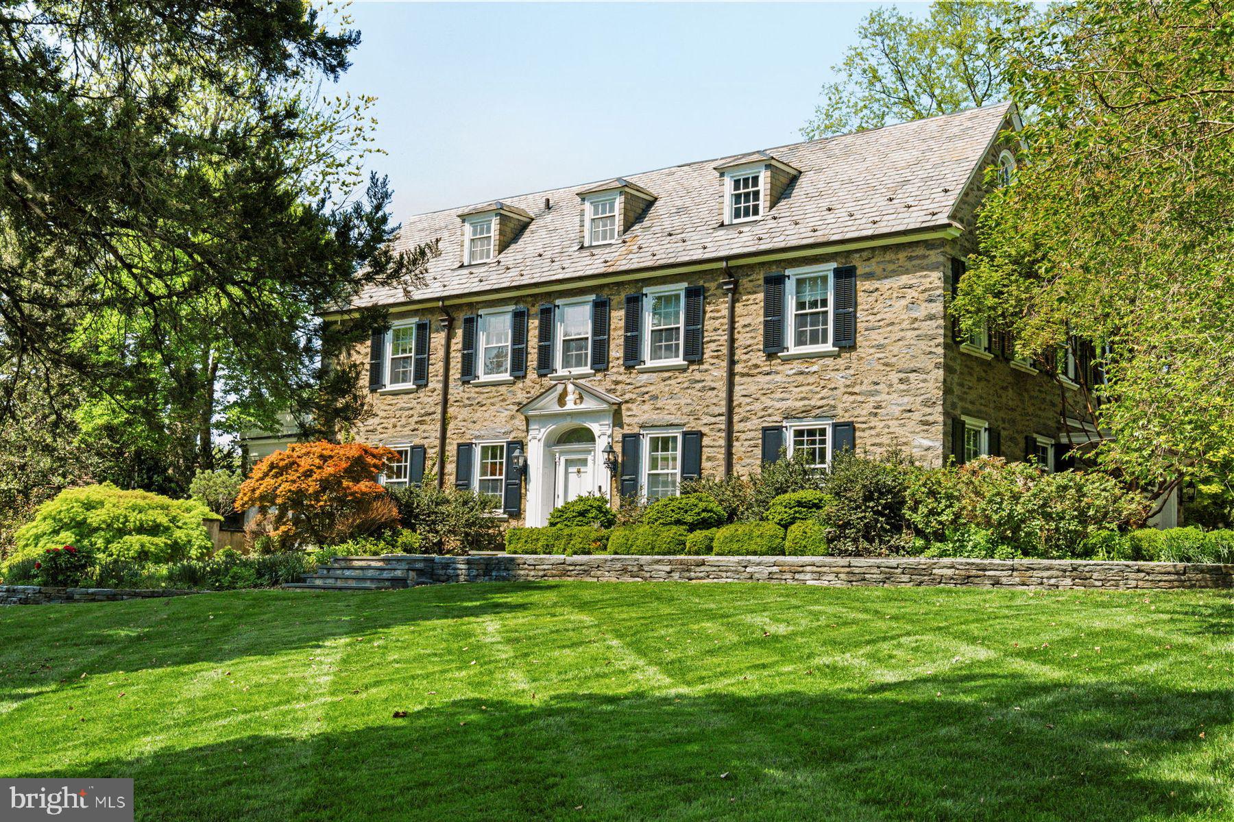 Introducing 9 Norman Lane, a distinguished Chestnut Hill residence with origins dating to the year 1890 and further shaped in 1926 for W. C. Tuttle. Designed by Hodgens & Hill and built by the Haverstick-Borthwick Company, the home reflects the enduring principles of Colonial Revival architecture. Set on 1.02 acres, this 5 bedroom, 3.5 bath home offers approximately 5,700 square feet of living space.

A gently rising drive lined with stone walls leads to the residence, positioned above its surroundings with stunning views of lawn and treetops, evoking the character of a European country house. Inside, a gracious foyer with a sweeping curved staircase introduces well-proportioned living spaces defined by original hardwood floors, detailed millwork, and stately fireplaces. The living room opens to a sunroom overlooking the pool and gardens, while the dining room features custom built-ins, a fireplace, and a statement crystal chandelier. A light-filled family room with floor-to-ceiling windows, built-ins, and wet bar connects seamlessly to the outdoors. The kitchen is appointed with custom cabinetry, marble countertops, a center island, and professional-grade appliances, including Sub-Zero and Viking, with an adjacent laundry room.

The second level features an expansive primary suite with private terrace, ensuite bath with soaking tub and walk-in shower, and a boutique-style dressing room. Two additional bedrooms and full baths complete this level. The third floor offers two bedrooms, a Jack-and-Jill bath, and a cedar closet.

Outdoor spaces include spectacular flagstone terraces, stone walls, a pool with a sculptural stone fountain and outdoor shower, creating a setting reminiscent of a European retreat. A detached stone structure houses pool equipment, echoing the home’s architectural character.

With its elevated setting and landscape defined by mature trees and thoughtful design, 9 Norman Lane offers a rare opportunity to own a home where architecture, setting, and livability come together with quiet distinction. Just minutes from charming shops, acclaimed restaurants, the scenic Wissahickon trails, and convenient train access to Center City Philadelphia, Manhattan and DC, this is where historic charm meets modern lifestyle. Discover the warmth, character, and quiet grandeur of 9 Norman Lane; a home where every detail tells a story.