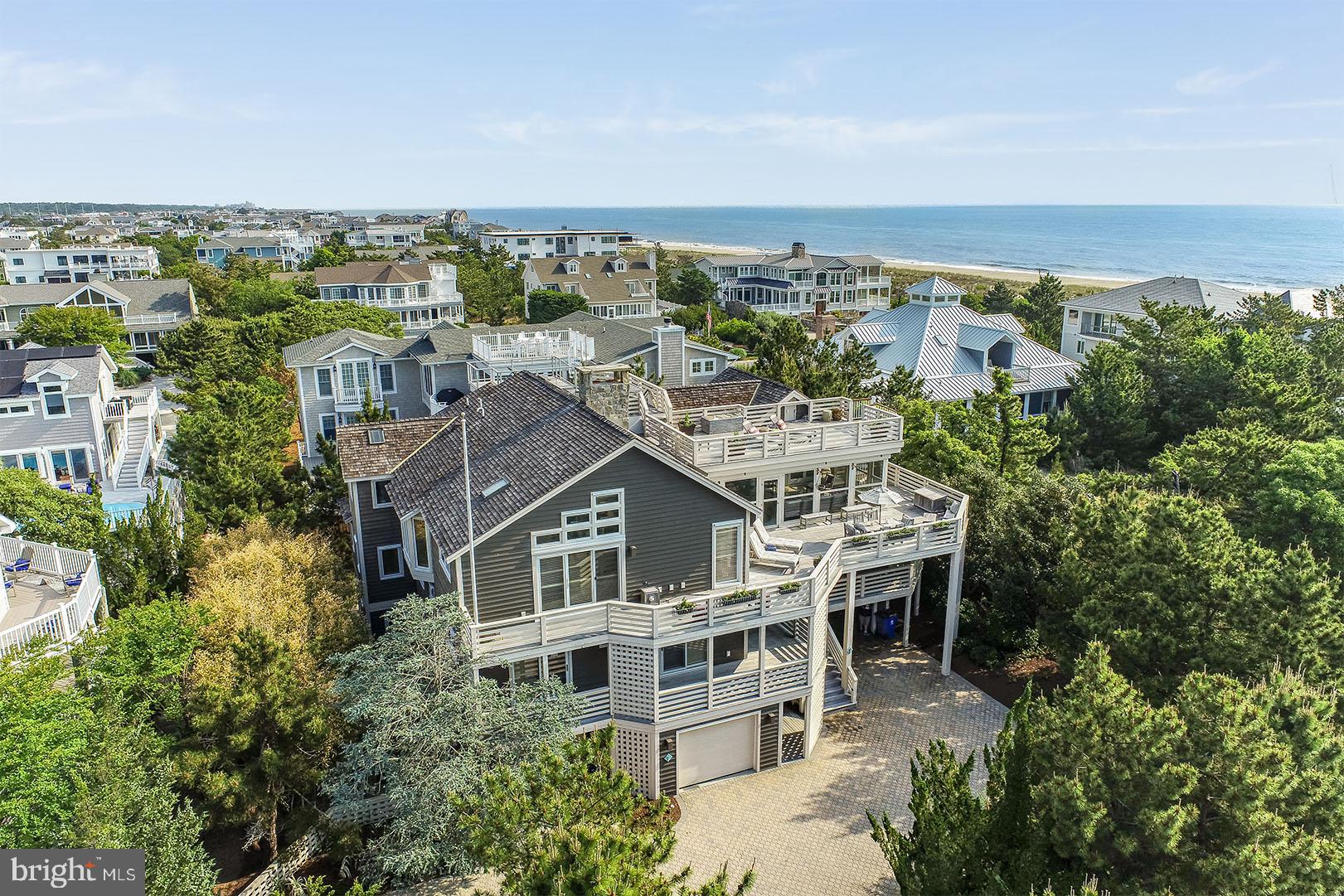 Welcome to 7 Hall Avenue in Indian Beach. This tastefully appointed custom home by Boardwalk Builders offers convenience to the community’s beautiful private beach. This location offers miles of coastline for peaceful walks, morning jogs or beach combing. 7 Hall Avenue is also conveniently located across from the Rehoboth Beach Sailing Association, and less than a quarter of a mile to the Rehoboth Bay Marina – ideal for boating and water sport enthusiasts. Situated in close proximity to downtown Dewey and Rehoboth Beach, this location leaves little to be desired. Offering +/- 5,200 square feet of heated living space, this custom-built residence features a very functional and open, 3-level floor plan complete with elevator access to each level. Upon entry, guests will be welcomed by beautiful travertine tiled floors, 2-story open hallway featuring a wood burning fireplace, 5 bedrooms each with private, en-suite baths, a laundry room and a spacious game room/office area featuring custom built-ins and a private half bath. A gorgeous open staircase will lead you to the third level featuring a gourmet kitchen with Wolfe and Subzero appliances, large breakfast bar and plenty of storage. A dining area neighbors the kitchen and is situated central to the living spaces making it ideal for entertaining and gatherings. This level is drenched with sunlight from the many floor to ceiling windows and skylights and features a beautiful stone, wood burning fireplace. This level also includes a cozy den, complete with a beverage fridge, ice maker, and wet bar as well as the master suite. The master bedroom is spacious and offers private access to the relaxing screened porch. The ground level of the home also offers travertine floors, and easy access to a full bath which is accessible from outdoors, perfect for beach breaks. This level is also home to spacious garages, ideal for vehicles and beach toys and a spa-style outdoor shower. The home’s numerous sun decks and screened porch offer superb exterior living. Take in ocean views and phenomenal sunsets from the rooftop perch which is ideal for morning yoga or an after-dinner night cap. This home is being sold mostly furnished and ready for this season's enjoyment.  7 Hall Avenue should not be overlooked!
