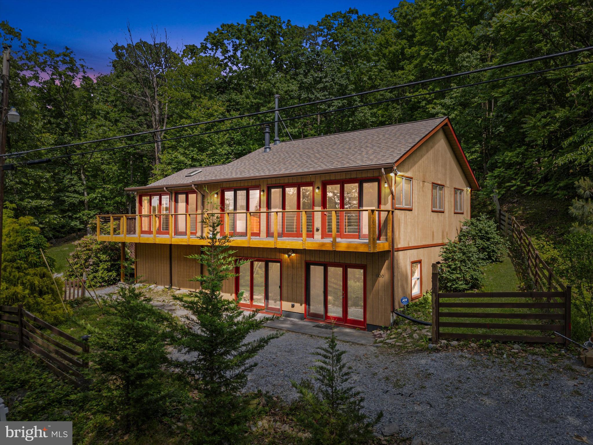 Come see this secluded mountain retreat with a European flavor backing to the Appalachian Trail and just minutes from the Shenandoah River! This three bed, two bath home has a long balcony overlooking the valley and lovely peekaboo views all along the property and from the interior skylights. Enter the home from the lovely deck off the kitchen where you can set up your grill and summer furniture to enjoy the outdoor living space. Additionally, there is a stunning sunroom that opens to the lengthy balcony, which was recently rebuilt to be enjoyed for many more years to come. 
The living room with hardwood floors, and a cozy woodstove is open to the eat-in kitchen that boasts ceramic tile floors, stainless steel appliances, an island with seating, and a separate dining area. There are skylights, exposed beams, and vaulted ceilings in the kitchen and living room that give the home that “mountain retreat” feel. Even the freestanding bathtub in the primary bedroom’s en suite has a gorgeous view and floods of light. The primary bedroom, second full bedroom and a second full bath are located on the main level of this home. Downstairs is another long bank of windows, a full bedroom, a large recreation room, and a spacious closet/bonus room. From the back garden, a gate leads to the mountain land owned by the Appalachian Trail. Climb up the trails through the wild and wonderful woods of West Virginia and be assured that this unrestricted property will always remain private.