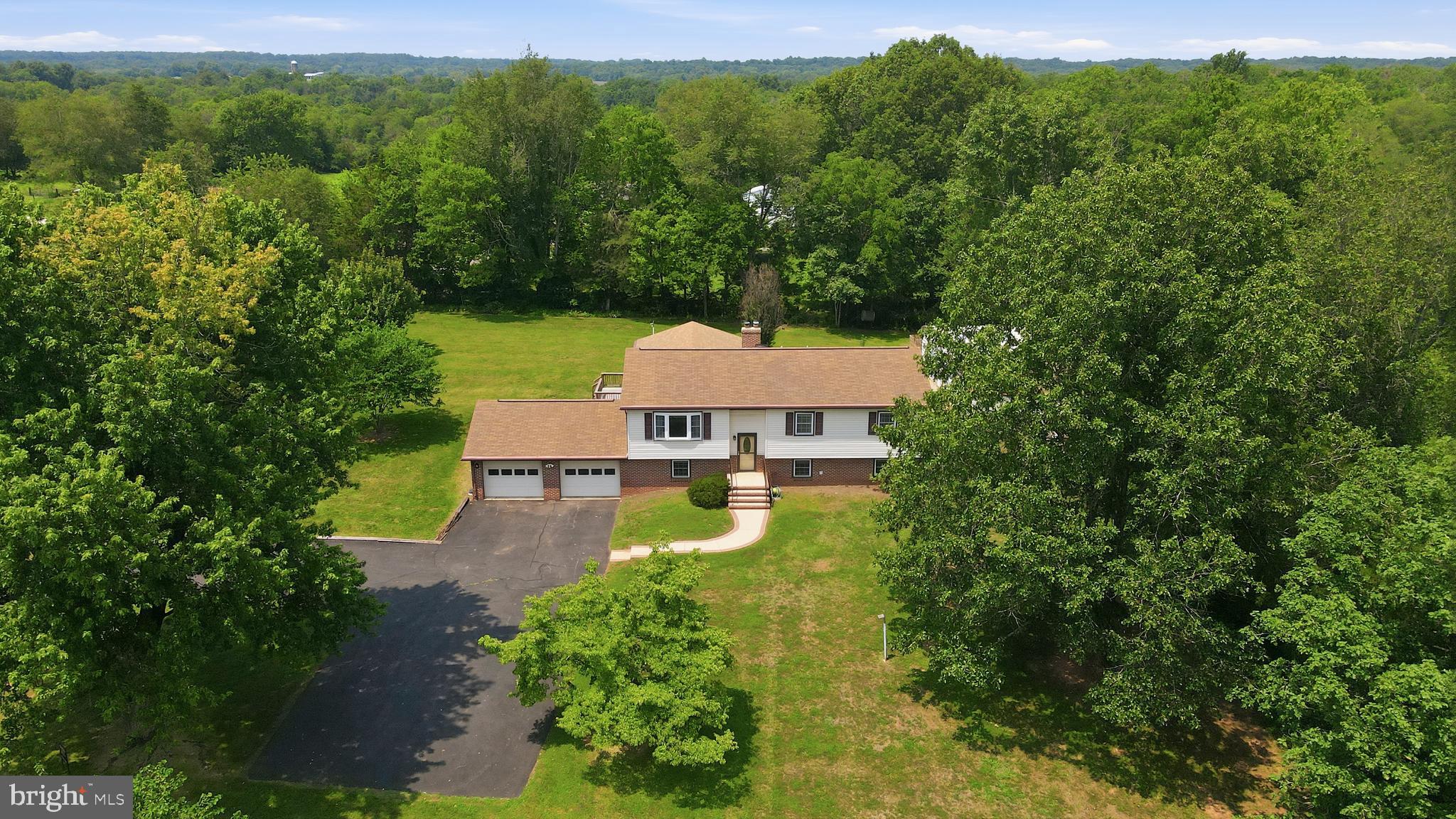 Tucked into the peaceful countryside of Catlett, this beautifully maintained home offers the rare combination buyers crave: privacy, nearly three-level acres, and an impressive amount of flexible living space. Set on 2.87 flat, usable acres, the property feels wonderfully removed from the rush of everyday life while remaining within reach of Warrenton, Nokesville, Manassas and the conveniences found along Route 28. Catlett’s rural Fauquier County setting is known for its open landscapes, generous properties and relaxed pace, making this an ideal retreat for anyone seeking more space without venturing too far from Northern Virginia.

The upper main level welcomes you with a large, light-filled living room where hardwood flooring and crown molding lend a timeless sense of warmth. At the heart of the home, the exceptionally spacious eat-in kitchen is designed for both everyday living and effortless entertaining. Granite countertops, stainless steel appliances, tile flooring, and abundant cabinetry provide style and function, while custom built-in shelving and storage add character to the breakfast area.

From the kitchen, step directly onto the oversized screened porch—an inviting outdoor living room with a vaulted ceiling and ceiling fan. Whether enjoying quiet mornings, hosting summer dinners, or watching the seasons change across the backyard, this is the kind of space that quickly becomes a favorite gathering place.

The primary bedroom is privately positioned overlooking the rear grounds and features two closets and an ensuite bath with tile flooring and a tub/shower combination. Two additional bedrooms face the front of the property and share a full hall bath, creating a comfortable and practical upper-level layout.

Downstairs, the home continues to surprise with an expansive family room accented by beautiful moldings, recessed lighting, built-in shelving, and a wood stove that creates a warm and welcoming focal point. Direct access to the two-car garage adds everyday convenience, while two additional generously sized rooms—each offering a closet—provide remarkable flexibility. Although the property’s septic system is approved for three bedrooms, these lower-level rooms could serve beautifully as guest spaces, home offices, hobby rooms, fitness areas or additional private retreats.

Outside, the setting is nothing short of serene. The broad, level backyard offers a peaceful canvas for recreation, gardening, outdoor entertaining or simply relaxing beneath an open sky. There is space to spread out, play, gather and enjoy the freedom that nearly three acres can provide. Two storage sheds sit on concrete slabs, including one equipped with electricity—perfect for equipment, tools, projects or workshop use.

Meticulously cared for and thoughtfully maintained, this property offers far more than a home. It is a private country retreat with room to grow, space to gather and possibilities in every direction. Here, tranquility is not something reserved for weekends—it is part of everyday life.