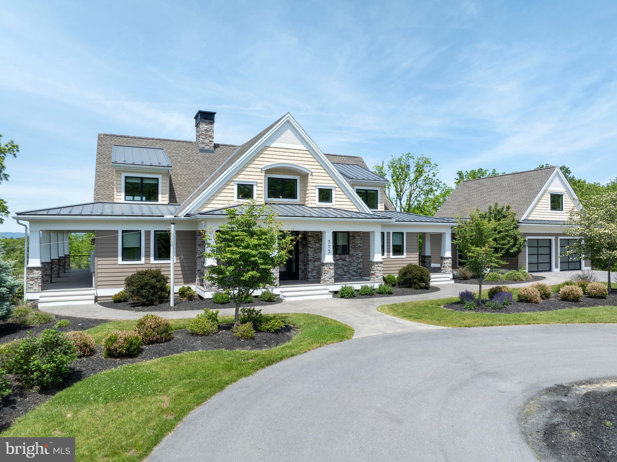 Welcome to a truly exceptional Craftsman estate where timeless architecture meets modern luxury, set on 16.56 breathtaking acres of rolling beauty and serene privacy. This remarkable 4-bedroom, 5½-bath home offers the perfect blend of refined living and relaxed comfort, thoughtfully designed for both everyday enjoyment and unforgettable gatherings. Step inside to discover a warm, open main level filled with natural light and refined finishes. At the heart of the home, the expansive chef’s kitchen is a true showpiece—featuring high-end appliances, generous counter space, custom cabinetry, aesthetically pleasing lighting and an inviting layout that makes cooking and entertaining effortless. Whether hosting holiday celebrations or enjoying a quiet morning coffee, this space was designed to bring people together. The adjoining living area flows beautifully, offering cozy yet sophisticated spaces anchored by Craftsman-style details and picturesque views of the surrounding acreage. Large windows frame the natural landscape, creating a seamless connection between indoor comfort and outdoor beauty. Throughout the home, each of the bedrooms offers privacy and comfort, while the 5½ bathrooms provide convenience and thoughtful design. The luxurious primary suite serves as a peaceful sanctuary, offering ample space to unwind at the end of the day. Downstairs, the fully finished lower level expands the home’s versatility even further. A complete second kitchen makes this level ideal for extended family living, guest accommodations, or effortless entertaining. Whether hosting long-term visitors or creating the ultimate game and movie night space, this level offers endless possibilities. Above the main-level two-car garage, a separate living space provides even more versatility. Perfect for a guest suite, home office, studio, or private retreat, it adds yet another layer of functionality to this already exceptional property. In addition to the main-level garage, a second two-car garage on the lower level ensures abundant storage for vehicles, equipment, or recreational toys.
Perhaps the most enchanting feature of all is the covered porch that stretches across the entire back of the home. This expansive outdoor living space invites you to slow down and savor the views—morning sunrises, golden afternoons, and peaceful evenings surrounded by nature. With 16.56 acres to explore, complete with scenic walking paths, you’ll enjoy privacy, beauty, and room to roam right outside your door.
This is more than a home—it’s a lifestyle. A rare opportunity to own a Craftsman estate where luxury, land, and livability come together in perfect harmony. (Some photos have been virtually staged.)