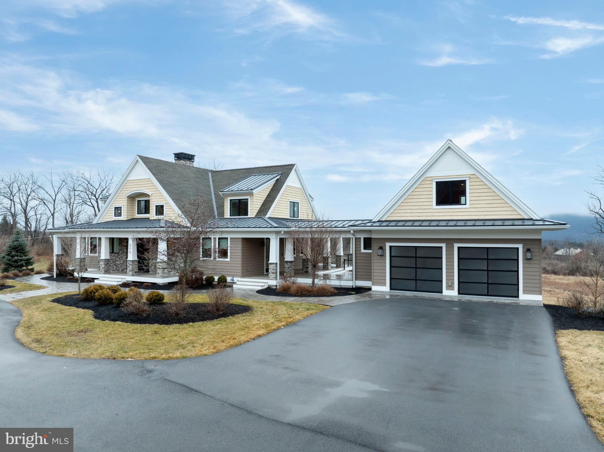 Welcome to a truly exceptional Craftsman estate where timeless architecture meets modern luxury, set on 16.56 breathtaking acres of rolling beauty and serene privacy. This remarkable 4-bedroom, 5½-bath home offers the perfect blend of refined living and relaxed comfort, thoughtfully designed for both everyday enjoyment and unforgettable gatherings. Step inside to discover a warm, open main level filled with natural light and refined finishes. At the heart of the home, the expansive chef’s kitchen is a true showpiece—featuring high-end appliances, generous counter space, custom cabinetry, aesthetically pleasing lighting and an inviting layout that makes cooking and entertaining effortless. Whether hosting holiday celebrations or enjoying a quiet morning coffee, this space was designed to bring people together. The adjoining living area flows beautifully, offering cozy yet sophisticated spaces anchored by Craftsman-style details and picturesque views of the surrounding acreage. Large windows frame the natural landscape, creating a seamless connection between indoor comfort and outdoor beauty. Throughout the home, each of the bedrooms offers privacy and comfort, while the 5½ bathrooms provide convenience and thoughtful design. The luxurious primary suite serves as a peaceful sanctuary, offering ample space to unwind at the end of the day. Downstairs, the fully finished lower level expands the home’s versatility even further. A complete second kitchen makes this level ideal for extended family living, guest accommodations, or effortless entertaining. Whether hosting long-term visitors or creating the ultimate game and movie night space, this level offers endless possibilities. Above the main-level two-car garage, a separate living space provides even more versatility. Perfect for a guest suite, home office, studio, or private retreat, it adds yet another layer of functionality to this already exceptional property. In addition to the main-level garage, a second two-car garage on the lower level ensures abundant storage for vehicles, equipment, or recreational toys.
Perhaps the most enchanting feature of all is the covered porch that stretches across the entire back of the home. This expansive outdoor living space invites you to slow down and savor the views—morning sunrises, golden afternoons, and peaceful evenings surrounded by nature. With 16.56 acres to explore, complete with scenic walking paths, you’ll enjoy privacy, beauty, and room to roam right outside your door.
This is more than a home—it’s a lifestyle. A rare opportunity to own a Craftsman estate where luxury, land, and livability come together in perfect harmony. (Some photos have been virtually staged.)