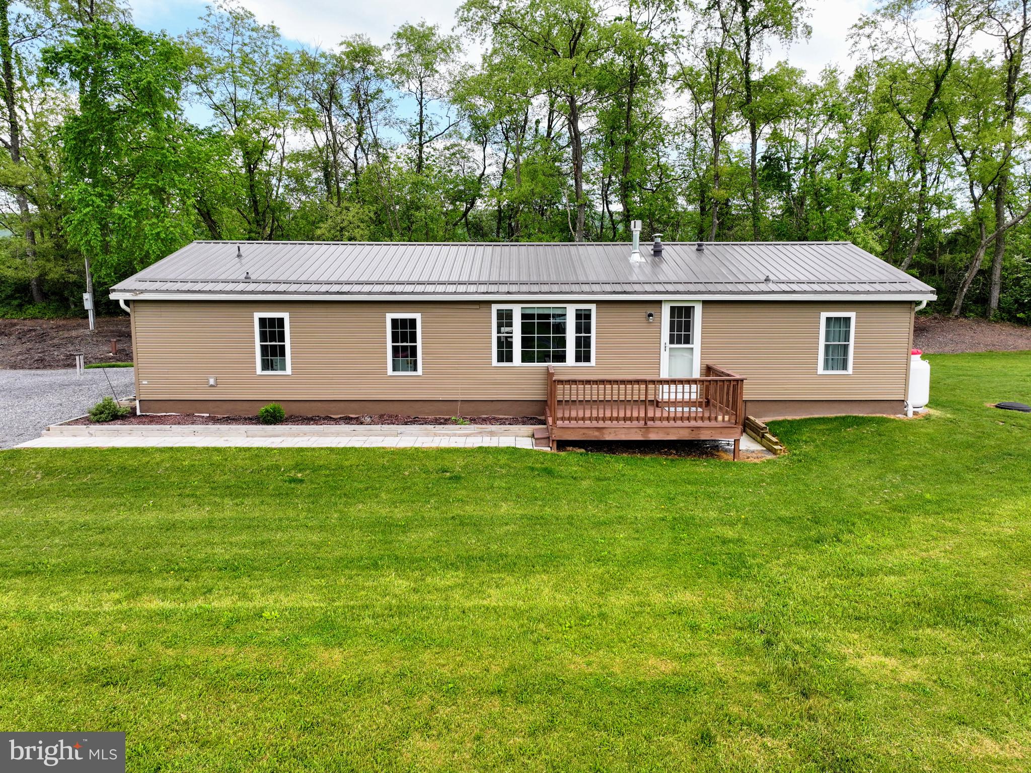 Who doesn't like a room with a view! This newly updated ranch sits on 3 beautiful, serene acres in Bedford County. This retired doublewide is secure on concrete blocks. In 2020 a new (40 year) roof, siding, windows, and doors were completed. A front deck, paver sidewalks and large concrete patio are ready for company! The back embankment is ready for you to add whatever annuals or shrubs you want to plant and make it yours. Inside, this home boasts of 3 bedrooms and 2 full baths. A laundry area and a breakfast nook let in plenty of sunshine. A perfect area for all of your plants! The galley kitchen has newer cabinets and countertops and has plenty of storage. Full open concept living with the dining and living areas. There is access to walk out onto the back patio from the dining room. From the living area you can cozy up and enjoy the warmth of the brand new (2024) stone and propane fireplace! Or take your gaze right out of the large family window and take in the views of the Allegheny Mountains! Beautiful farm land and neighbors spotted around. Even with 220 South nearby, the traffic noise is not a problem. The master bedroom has plush carpet and is large enough for a king bed and furniture. A large closet and an immaculate master bath make this bedroom perfect. Open the french doors to the bonus room and make it your own space -an office, art or craft room, or even a 4th bedroom. It's even complete with a closet. At the other end of the home is another full bath for guests, and two bedrooms with closets and plush carpet. If you're handy or need a work shop, you won't be disappointed. A brand new electric garage door and new epoxy floor are waiting for you inside this 29'x15'3'' garage with work space counters and storage space. Park your car, motorcycles, truck or large RV in here if you desire. A 28'x12' Shawnee Structure has been added for even MORE storage. And it doesn't stop there! There have been custom blinds made for inside the home, keyless entry, a Vivint Security system ready to go; and then outside you'll find an underground pet fence that gives a large range for your furry friends to roam! And never get on the roof to clean a gutter again... this home comes with Leaf Filter on the gutters, with a lifetime warranty. An outdoor fire pit and lots of extra wood are included along with a freeze free spigot to hook up your garden hose to for all those summer water games or to water your garden. Any which way you look at it, this home is a must see. Close to Bedford and Cumberland, or a short drive to Rt 30 or the turnpike, this home is sure to please!
