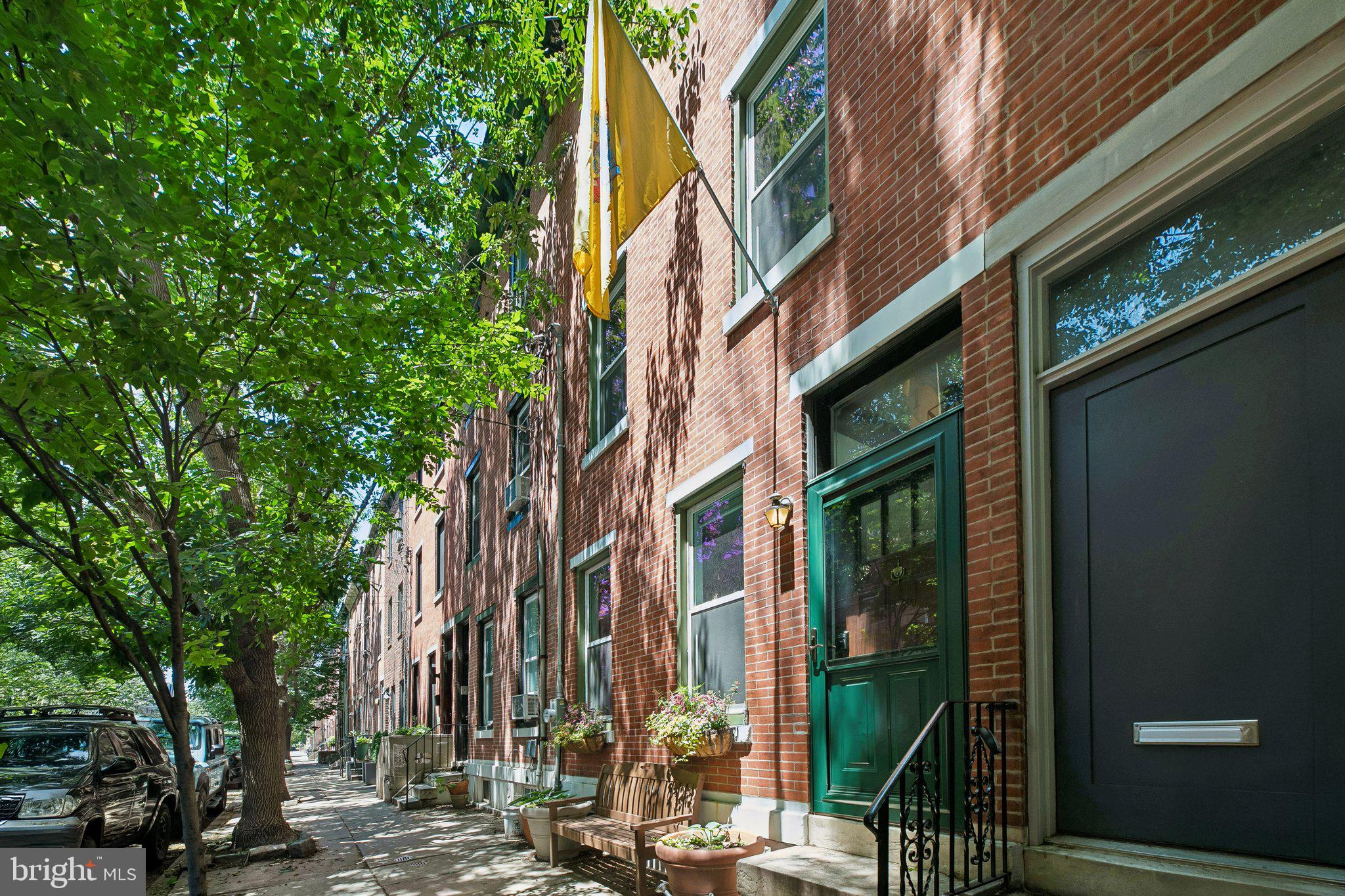 Updated 4-bedroom, 2.5-bath home in the Greenfield Catchment with a finished basement and private patio, seamlessly blending historic Philadelphia charm with modern design. Step inside to an expansive open-concept main level featuring exposed brick walls, soaring ceilings, hardwood floors, and a striking marble fireplace that anchors the inviting living space. The seamless layout flows into a spacious dining area with custom built-ins and a conveniently located powder room, creating an ideal setting for both everyday living and entertaining. The oversized kitchen offers abundant cabinetry, granite countertops, stainless steel appliances, a breakfast bar, and ample prep space. Just beyond the kitchen, the private rear patio provides the perfect outdoor retreat for dining al fresco, gardening, or relaxing with friends and family. The second floor is home to the spacious primary suite, featuring ample closet space and a versatile adjoining flex room that can serve as a fifth bedroom, home office, nursery, dressing room, or walk-in closet. This level also includes a beautifully renovated full bathroom showcasing designer finishes, a luxurious soaking tub, separate glass-enclosed shower, double vanity, and stunning emerald-green tile. A dedicated laundry area with stacked washer and dryer and custom cabinetry adds everyday convenience. The third floor offers three additional spacious bedrooms and another updated full bathroom. The finished basement adds valuable living space ideal for a media room, playroom, gym, or home office, while also offering additional storage. Perfectly situated just steps from South Street's vibrant dining and shopping, this home places some of the neighborhood's favorite destinations right outside your door, including Loco Pez, Sabrina's Cafe, Social House, and City Fitness. Enjoy easy access to Center City, Penn, CHOP, and the University of Pennsylvania, making this location ideal for those seeking the perfect blend of convenience, walkability, and city living.
