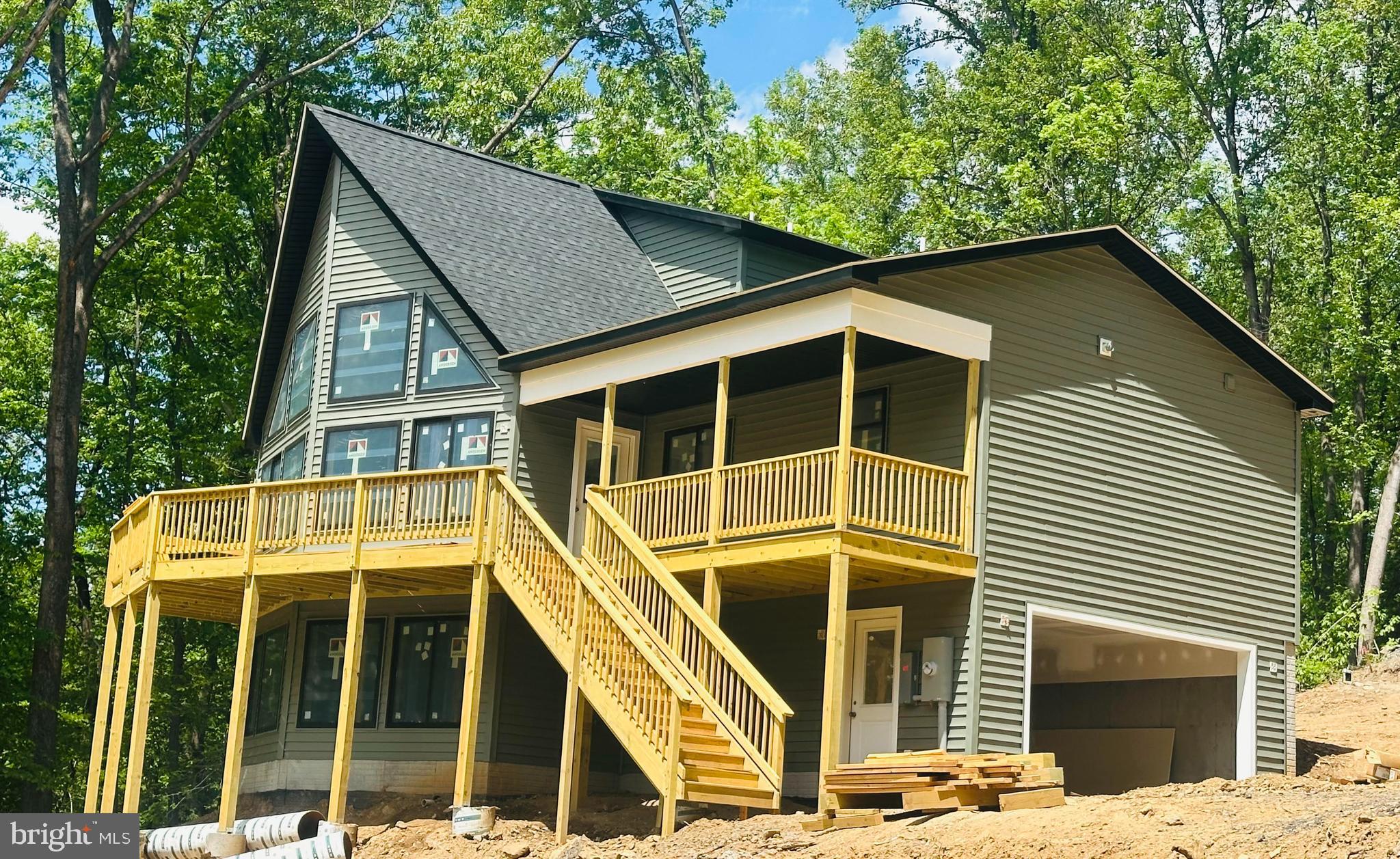 This stunning new construction chalet is nearing completion and offers the perfect blend of modern comfort and peaceful mountain living. Nestled on 1.3 wooded acres in desirable Shenandoah Farms, this 3-bedroom, 2½-bath home invites you to embrace the beauty, privacy, and slower pace of country life while still enjoying convenient commuter access. Whether you’re searching for a full-time residence, relaxing weekend retreat, or potential short-term rental investment (with county approval), this property checks every box.

Shenandoah Farms is a scenic mountain community in eastern Warren County featuring two private mountain lakes, deeded access to the Shenandoah River, recreation areas, and playgrounds for residents to enjoy year-round. Here, outdoor adventure and everyday tranquility go hand in hand.

Inside, the thoughtfully designed open floor plan is highlighted by soaring cathedral ceilings and expansive windows that fill the home with natural light and bring the surrounding beauty indoors. The main level features a spacious kitchen, dining, and living area, along with a laundry/pantry room, half bath, and a private primary suite complete with a luxurious bath. Upstairs, you’ll find two additional bedrooms and a full bath, offering plenty of space for family and guests. The unfinished basement is already roughed in for a future bath and framed for additional living space, while also providing a two-car garage.

Step outside and unwind on the large covered and open front deck — the perfect place to sip your morning coffee, entertain friends, or simply relax and take in the peaceful surroundings. A covered 12x10 entry porch adds even more charm and functionality.

Quality finishes throughout include a beautiful propane direct-vent fireplace with real stone surround and wood mantel, hardwood flooring on both levels, and tile bathrooms. The luxurious primary bath features a double vanity and a gorgeous walk-in tile shower with frameless glass door. The kitchen is beautifully appointed with Wolf Classic cabinetry in a warm vanilla finish, dovetail drawers, soft-close doors, quartz countertops, and stainless steel appliances.

Located in scenic Warren County, this home places you just minutes from wineries, breweries, Shenandoah National Park, the Appalachian Trail, the Shenandoah River, and the charming shops and restaurants of historic Front Royal. Experience the best of mountain and country living in a home designed for both relaxation and adventure.