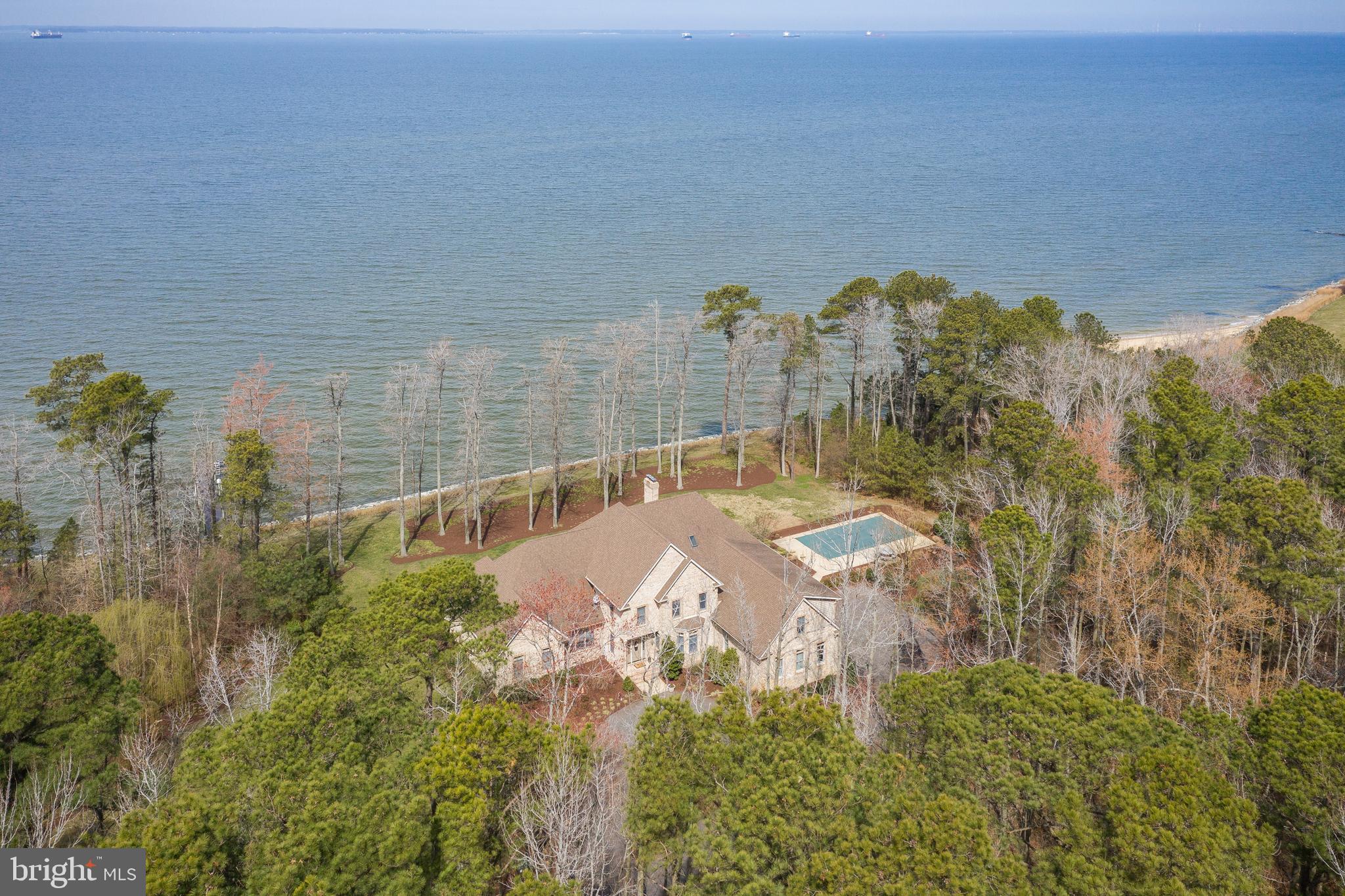 Incredible waterfront, with a Bay view! Watch cruise ships and barges travel by from the comfort of your screened-in porch. Sunsets with Western exposure offer the perfect backdrop to wind down for the evening. This property provides ample privacy on a plush 5.6-acre lot. As the paved winding driveway leads to a meticulously maintained, brick showstopper. Enjoy the spacious layout with an open floorplan, 4 bedrooms, 5.5 bathrooms, grand closets, & a 20' ceiling in the living room. The 1st level houses a Master Bedroom w/ en suite, along with another bedroom & full bath. On colder nights you can cozy up to the stone fireplace w/ pellet stove insert. The transition to warmer days will feel amazing knowing you can go for a swim in your inground pool, or partake in water activities from the convenience of your pier with lifts. If you prefer to be indoors, then the bonus game/theatre room is a perfect match. And to think, all of this while being minutes from Rt 50, the bridge, & quick access to local attractions. Come and see, this home has it all.