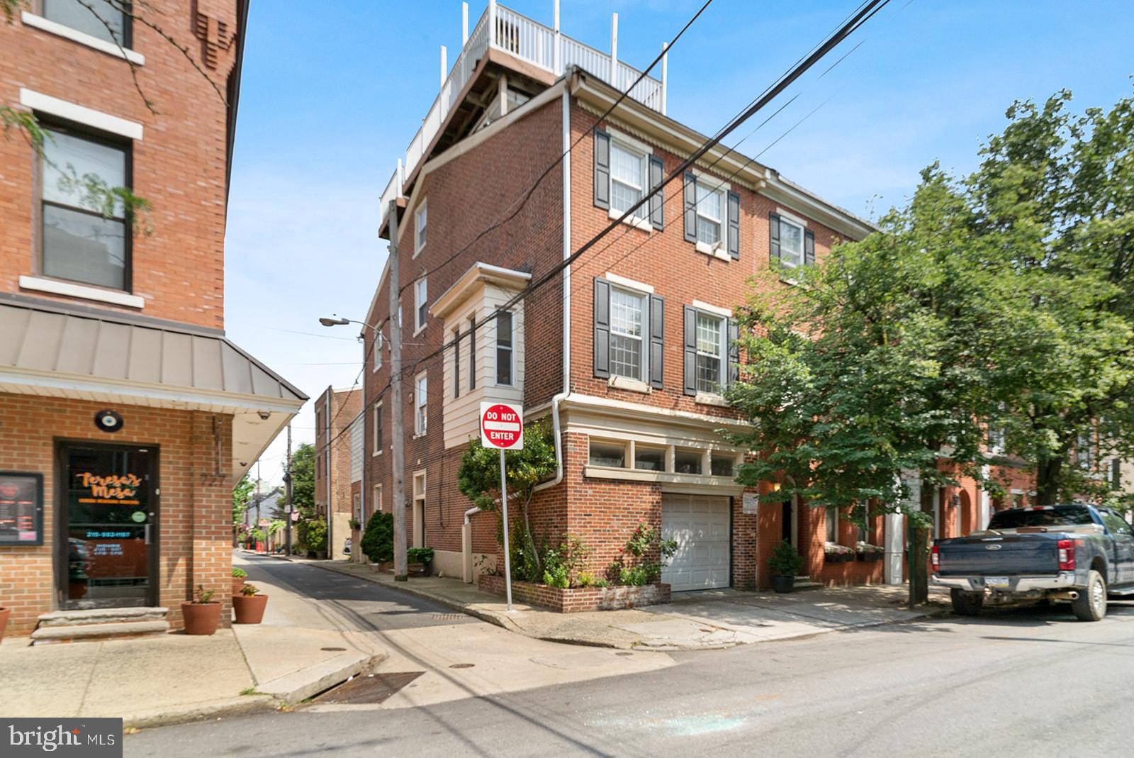 Immense charm and character shine through in this very unique corner townhome condo in the heart of Queen Village offering 2/3 bedrooms, 1.5 baths, an oversized 1-car garage, 3 exposures, den, terrace, dramatic rooftop deck, and a partially finished basement. This home begins with an open foyer area offering a powder room, 2 closets, and a door to the garage. On the second floor, you'll find the wide-open living and dining space complete with high ceilings, a bay window with a built-in window seat, crown molding, built-in shelving and cabinetry, a wood fireplace, and new hardwood floors. This whole 2nd floor has been completely remodeled recently by the homeowner. The third floor offers a front bedroom with carpeting, two windows, two double mirror closets, a walk-in closet, and a brick mantle. Off the hall is a full bathroom recently renovated. This level offers an additional bedroom with an exposed brick wall, carpeting, and a double closet. Steps lead up to an amazing large open loft space, ideal for a den, office, or possible third bedroom, offering original pine floors, wood beam ceiling, exposed brick wall, 3 exposures a big walk-in closet, wet bar, and double sliding glass doors out to a covered terrace with fantastic views of the Delaware River. Follow spiral steps of the terrace up to the incredible rooftop deck which offers an outdoor kitchenette, built-in bench, hot tub, planters, lighting, and incredible 360-degree views! The partially finished basement offers laundry, mechanicals, and storage. This home is part of a condominium and is 1 of 2 units. The condo fee is $129/month and covers common insurance, water, and sewer only. Each owner is responsible for their own roof, exterior, snow removal, etc. The costs are split between the owners 50/50. This incredible home is located within the Meredith School Catchment and is located within walking distance to a multitude of shops, restaurants, cafes, and parks, plus Headhouse Square, Penns Landing, and easy transportation I95 N and S.