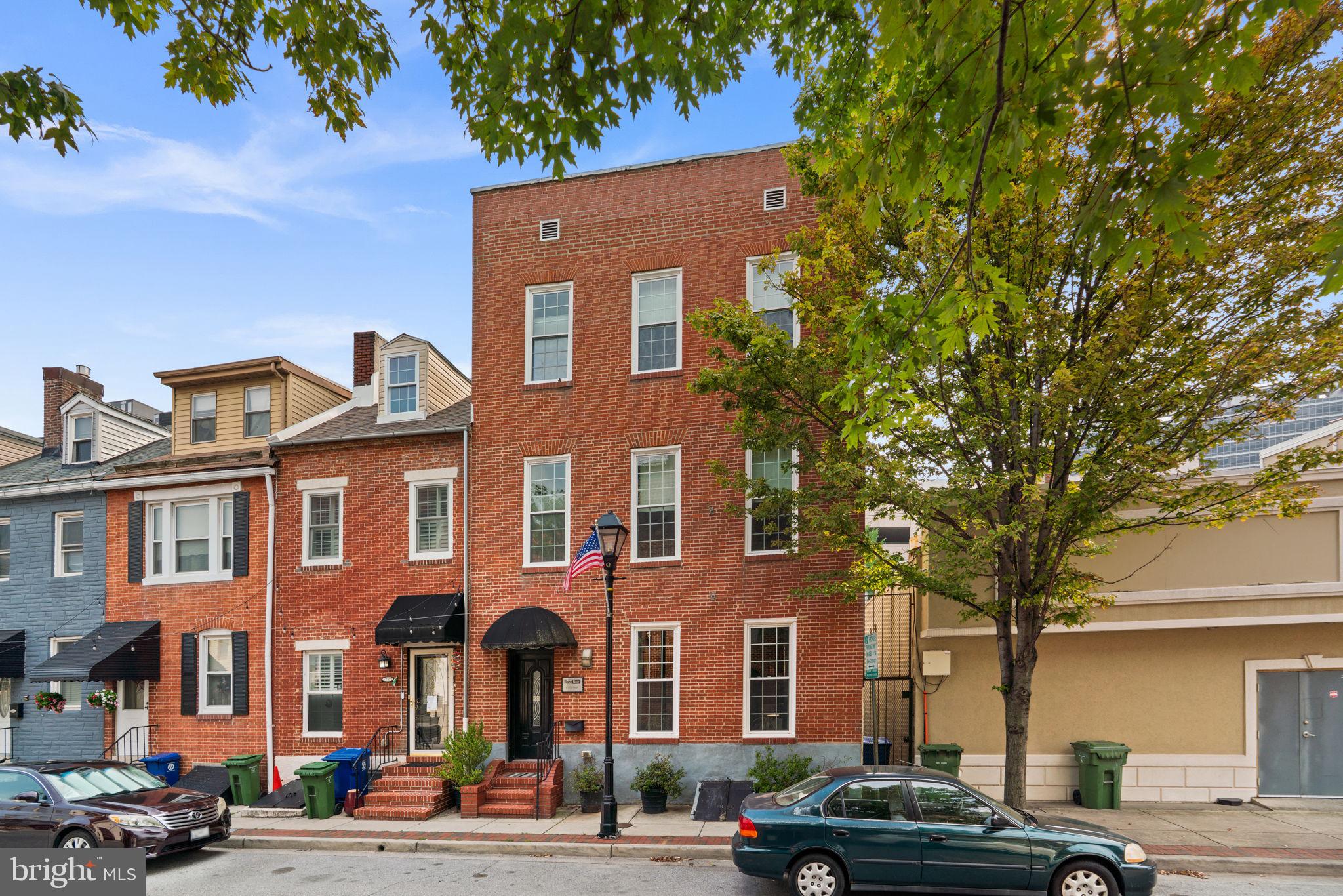 Rarely available and truly one-of-a-kind, this beautifully preserved and thoughtfully renovated rowhome offers 4 bedrooms, 5 full baths, 6,000 total square feet, a 4-car attached garage in the heart of Little Italy. Currently operated as a bed and breakfast, this extraordinary property presents an exceptional opportunity with remarkable residential and commercial potential, blending historic charm, eclectic design, and modern amenities throughout approximately 4,500 finished square feet. // Step inside to a striking main-level foyer featuring distinctive black-and-white checkerboard tile, which continues throughout the hallway and sets the tone for the home's unique character. Throughout the residence, original charm is complemented by gorgeous hardwood floors, custom details, and thoughtfully curated finishes. The main level offers an inviting living room centered around a floating built-in gas fireplace, creating a stunning focal point. Elegant French doors open into the formal dining room, complete with a contemporary chandelier and side access to a private patio. The modern eat-in kitchen is designed for both everyday living and entertaining, featuring upgraded countertops, sophisticated black cabinetry with glass-front upper cabinets, a stylish backsplash, stainless steel appliances, and additional access to the outdoor spaces. // The upper level features a versatile central living area, ideal for a family room, lounge, or shared gathering space, complete with a gas fireplace and access to the elevated balcony. Two spacious bedroom suites complete this level, each offering a private ensuite bathroom. One suite includes a custom built-in closet organization system and a luxurious bathroom with a large jetted corner soaking tub, separate shower with dual showerheads, and dual-sink vanity. The second suite features its own dual-sink vanity and standing shower. The top level continues the flexible layout with another central living space and two additional bedroom suites. One suite features a walk-in closet and a spa-inspired bathroom with a fully electronic spa tub with multiple jets, a separate shower with three shower heads, 1 rain shower and 2 standing showers, while the other offers a private bathroom with a dual-sink vanity and standing shower. Additionally, the bedrooms currently themed London and San Francisco feature mirrored closets. // The lower level adds even more versatility with checkerboard flooring throughout the recreation room, a bonus room, laundry room, utility room, and a convenient split bath featuring a separate shower and vanity area with an adjoining water closet, providing endless possibilities for guest accommodations, workspace, entertainment, or additional living areas. // Outdoor living is truly exceptional with multiple private spaces designed for relaxation and entertaining. Enjoy the private elevated balcony, a secluded side patio surrounded by flower planters and privacy features, an overhead awning, and flexible space for lounge seating or outdoor dining. Steps lead to the expansive rooftop deck above the garage, featuring turf, an electrically operated Sunsetter retractable awning, privacy walls, and French doors opening to a versatile interior bonus space complete with a wet bar. The four-car garage provides rare city parking and includes a convenient workshop area. // Located in the heart of Little Italy, this remarkable property places you among charming streets lined with iconic string lights, beloved Italian restaurants, and local shops. A rare feature in Little Italy, the property offers street access from both High Street and Albemarle Street, providing added convenience and accessibility. From your front door, easily explore Harbor East, the Inner Harbor, waterfront attractions, acclaimed dining, boutique shopping, and vibrant entertainment, all just minutes away. The sale also includes most furniture and décor, with select personal exclusions.