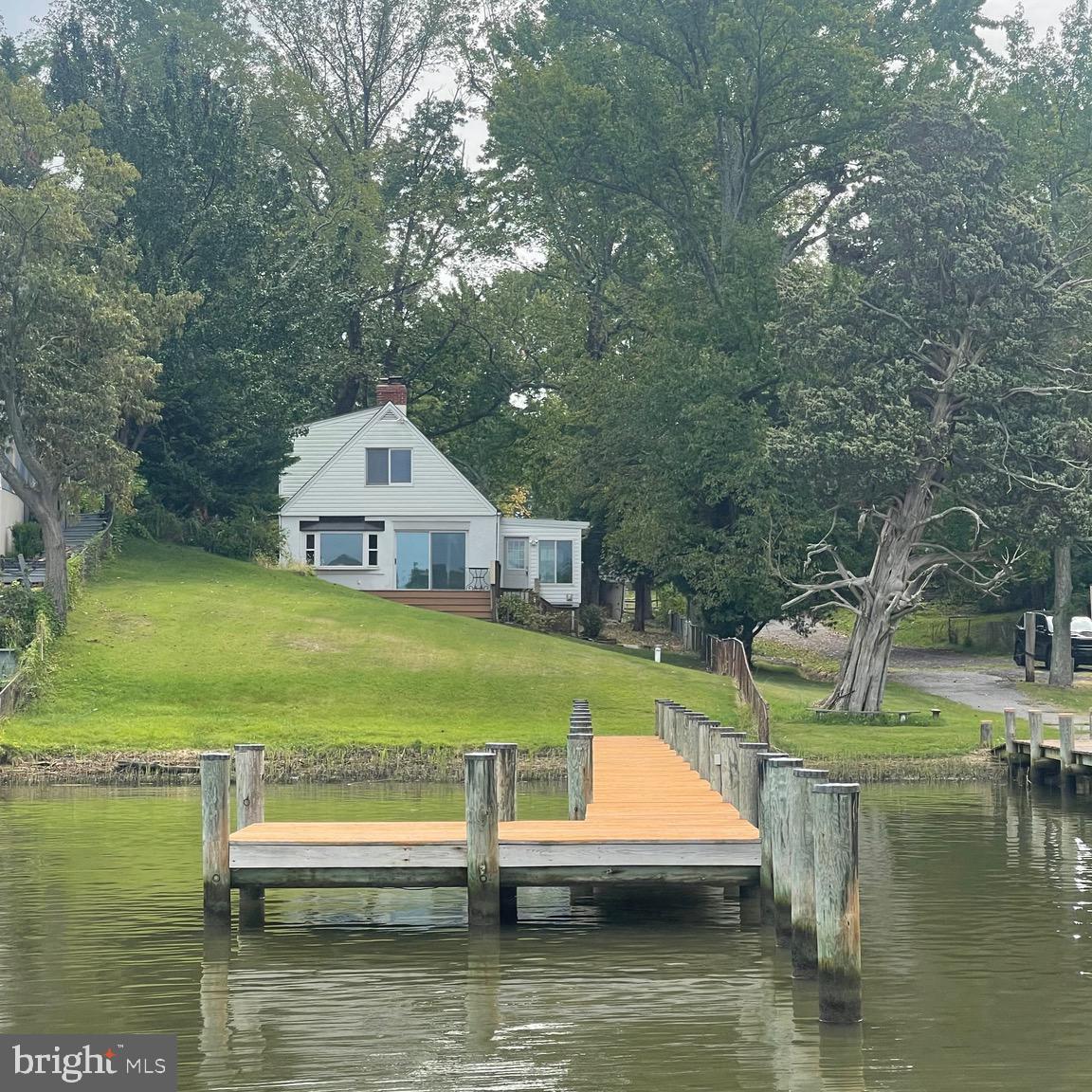 Spectacular .45 acre  waterfront gem just off the South River in the sought after Shoreham Beach community! Arrive by car or by boat, and enjoy the private dock for boating, fishing, crabbing, viewing the AMAZING sunsets and seasonal fireworks displays.  Enter the front of the home on the waterfront side into the sunroom with beautiful waterviews. The main level living room features a bay window and sliding glass doors to the deck facing the water and an updated full bathroom. Light and bright kitchen with corian countertops and separate dining room.  The upper level newly renovated full bathroom features a spacious shower with dual shower heads and Toto toilet. The primary bedroom has a large window overlooking the water and 2 closets, one a walk-in. The second bedroom overlooks the large rear yard.  The home is clean and updated with new luxury vinyl plank flooring, renovated full bathroom upstairs, updated main level full bathroom, fresh paint, replacement windows, new curtains and shades, hot water heater replaced in 2023, dryer replaced in 2023 and partial roof replacement in 2023. The rear of the home offers a fenced yard, shed and secure parking for 2-4 cars and/or boat trailer and the front of the home is your playground on the water. This home sits on the calm Ramsay Bay side of the Mayo Peninsula where you can boat, relax, swim, kayak or SUP. The end of the peninsula faces the mouth of the South River as it meets the Chesapeake Bay where you can watch the large ships pass through as they head in and out of Baltimore.   Mayo Beach Park is in the neighborhood and  Beverly Triton Beach is about 1 mile away, still on the peninsula.  The Shoreham Beach neighborhood is located within 45 minutes of DC and 20 minutes from Annapolis. There is a voluntary community association which allows access to the community dock and small boat ramp. There is a neighborhood private beach next to Mayo Park which faces the bay.  Riparian rights, private 110' long dock with 16' x 10' deck area at the end and 3 pilings extend 30' from the end of the dock.  Flood insurance is not required.