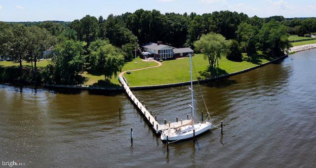 OPEN HOUSE HAS BEEN CANCELLED. Sellers accepted an offer. Sailor's Paradise on the Wye River with 8 feet MLW with a summer range about 8-10 feet. This unique property is on 2.88 acres with over 3600 square feet of living space nestled in the farmlands of Maryland in Talbot County. Three fireplaces, a wall of windows overlooking the Wye River, a cockpit/conversation pit in front of one of the fireplaces and a hanging table in the great room are just some of the things that make this such a unique home. Upon entering the home, one is greeted with a two story entrance hall that highlights the open floor plan. One is drawn, however, to the spectacular water view from the two story great room that has twelve 4’x8’ floor-to-ceiling picture windows over-looking a large expanse of lawn to the 450 feet of waterfront on the Wye River and the newly constructed pier. Across the river are only trees on Wye Island and the view of Dividing Creek, hence the name of the house “Dividing Views”. The beautiful blue ceiling of the great room is highlighted with a well-known constellation depicted in lights. The flooring is Pennsylvania blue slate. The home also offers the "River Room" with an indoor BBQ, quarry tile flooring, a stamped metal ceiling and two sides of glass that give a wonderful view of the Wye River. The pier was replaced in 2019 and is 5ft x 110 ft with an 8ft end platform. The slip has Tide Slides so you don't have to adjust the lines and an ice bubbler. Once you visit this property, you will not want to leave. When you find the right home it will speak to you. The owners hope Dividing Views says as much to you as it did to them. Welcome Home.