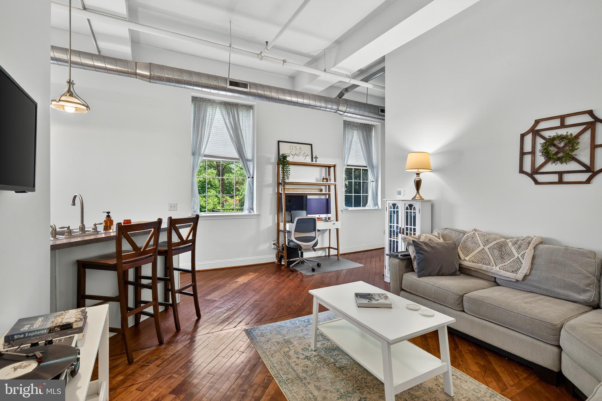 Rarely available Washington Mill Loft in the heart of downtown Phoenixville! This intimate 15-unit historic mill conversion offers a unique opportunity to own a true loft-style residence combining original architectural character with modern convenience. Unit #202 features soaring ceilings, oversized factory-style windows, beautifully preserved hardwood floors, exposed industrial details, and an open-concept layout filled with natural light. The updated kitchen features stainless appliances (2023), bright tall cabinetry, and breakfast bar seating that opens to the living and dining area—creating an ideal space for everyday living and entertaining. The spacious bedroom offers excellent closet space and convenient access toward the parking area. Additional highlights include in-unit laundry, elevator access, deeded off-street parking, a private basement storage room, secure entry, and a fenced community courtyard. Located steps from downtown Phoenixville's restaurants, breweries, coffee shops, boutiques, festivals, and entertainment, Washington Mill Lofts offers a rare combination of historic charm, convenience, and low-maintenance living.