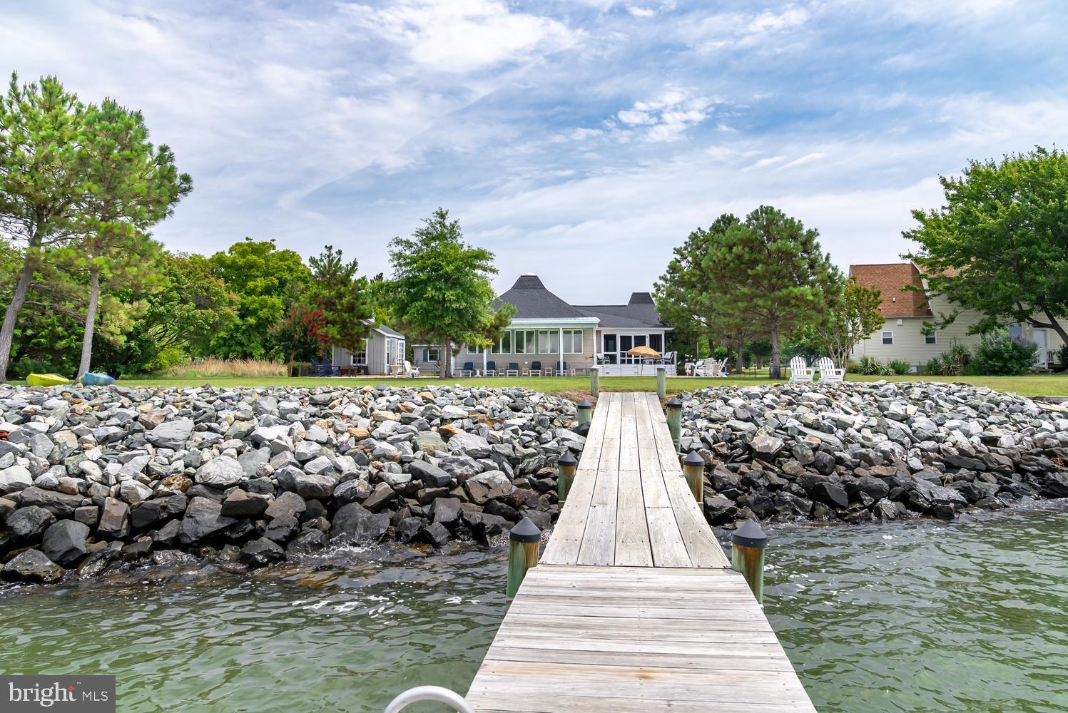 Experience Eastern Shore waterfront living in this charming Chesapeake Bay home, where breathtaking sunset views and a relaxed coastal atmosphere create the perfect setting for everyday living or weekend escapes. Designed to embrace the waterfront lifestyle, the property offers exceptional indoor and outdoor spaces for entertaining family and friends. A brick walkway welcomes you to the inviting front porch and foyer, where hardwood floors flow throughout the home. Recently renovated, the kitchen features white cabinetry, quartz countertops and large windows that fill the space with natural light while overlooking the front yard. The spacious living room is highlighted by a cathedral ceiling and opening to a year-round sunroom surrounded by walls of windows showcasing panoramic views of the Chesapeake Bay. The primary suite features a newly renovated bath with a tile and glass shower. Two guest bedrooms, an office and two additional beautifully renovated full baths occupy the opposite wing of the home, while the second level offers a fourth bedroom with skylights. Outside, you'll find everything needed to enjoy life on the water. The waterside pool with swim deck is complemented by a screened porch, expansive patio, covered seating area and a pool house/bar complete with air conditioning and electric. The private pier provides the perfect spot for fishing, crabbing, or simply taking in the spectacular sunsets, while the rip-rapped shoreline offers lasting shoreline protection. Additional improvements include an attached two-car garage, a storage shed with electric, and a new roof installed in 2025. Situated on high ground outside of the flood zone, this exceptional waterfront property offers direct access to some of the Chesapeake Bay's best fishing, boating, waterfront restaurants and the unforgettable Eastern Shore lifestyle.
